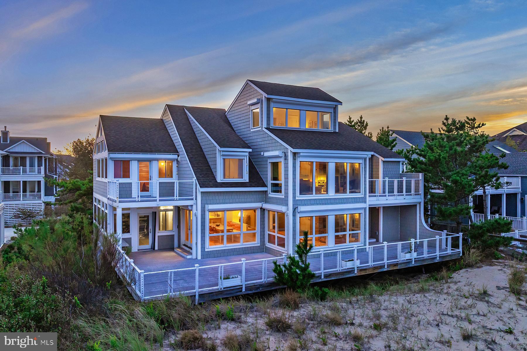Welcome to this exceptional oceanfront retreat, perfectly positioned within the exclusive gated community of Bayberry Dunes in North Bethany. Offering 75 feet of pristine ocean frontage, this coastal sanctuary captures breathtaking, unobstructed views of the Atlantic Ocean and provides direct access to a private lifeguarded beach. Architecturally designed for gatherings both large and intimate, the residence features five bedrooms, three and a half baths with a spacious additional family room, a built-in bunk bed room, and a private office that could easily serve as a sixth bedroom. Step inside to a sun-drenched great room where windows frame endless ocean vistas and open to an expansive main deck, a perfect setting for entertaining, relaxing, or simply savoring the sound of the waves. The main living area flows seamlessly across terracotta tile flooring, connecting the kitchen, dining area, and family room in a warm inviting layout. The kitchen features custom tile countertops and backsplash, ample cabinetry, and a convenient prep sink for the culinary enthusiast. Large glass doors open to a side enclosed porch, allowing the two dining areas to merge into one continuous space ideal for beachfront entertaining, all leading onto a full-length oceanfront deck. The main level radiates coastal charm with a wood-burning fireplace and two generous bedrooms. Upstairs, the oceanfront primary suite is a private haven, offering its own deck with panoramic ocean views, a luxurious en-suite bath with jacuzzi tub, walk-in tile shower, and bidet. An additional upstairs family room, with circular stairs leading to a cozy loft area, provides even more space for relaxation or recreation. The lower level offers elevated essentials, including covered porch areas, a large storage room for beach accessories, and an outdoor shower, all with direct access to the dune crossover and beach. Set on a large parcel within this private North Bethany community, the home enjoys the security of high elevation and natural dunes, while being just moments from the shops and restaurants of downtown Bethany Beach. Offered fully furnished and move-in ready, this home invites you to experience coastal living at its finest, whether as a cherished personal retreat or a savvy rental investment. Rental investment analysis available upon request. Additional highlights include composite decking, hurricane shutters, oceanfront dining areas, and parking for up to seven vehicles within the driveway and carport. Experience the timeless allure of the Delaware coast, schedule your private tour today and discover the potential of this extraordinary oceanfront property.