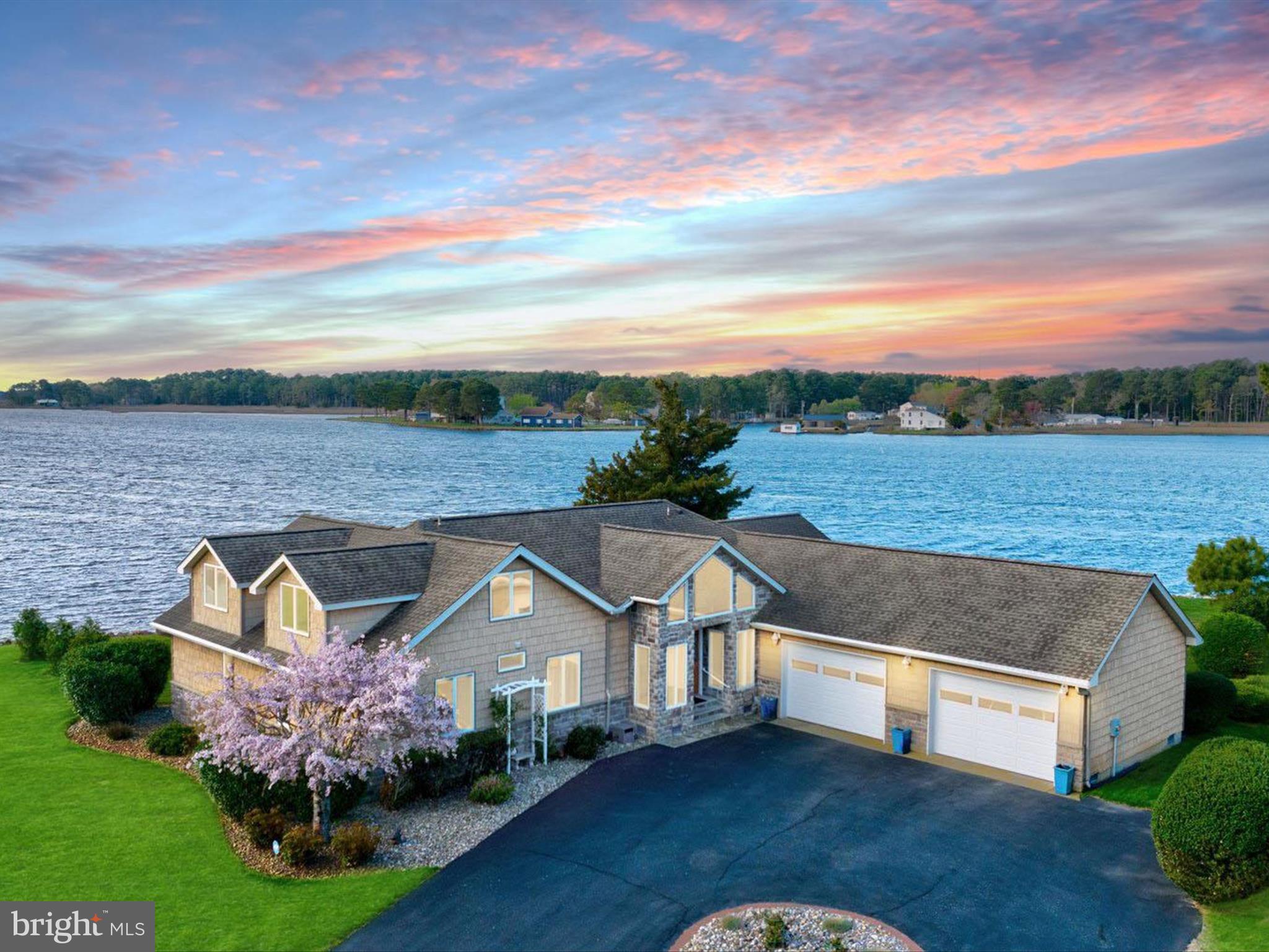 Introducing 13218 Rollie Road E. — a waterfront masterpiece where luxury living meets serene natural beauty. Perfectly positioned on Grays Creek as it opens into the majestic Assawoman Bay, this custom-built residence offers breathtaking panoramic views stretching to the Ocean City skyline. Just minutes from the vibrant beaches and resort towns of Delaware and Maryland, this extraordinary retreat promises the ultimate in coastal living.
 
Showcasing over 3,000 square feet of meticulously crafted living space, the home offers 5 bedrooms and 4 full baths, each thoughtfully designed to complement the home’s stunning surroundings. Situated on over 200 feet of rip-rapped shoreline, with a 62-foot pier, an 8,000 lb. boat lift, and no HOA restrictions, your waterfront adventures are only limited by your imagination. Step inside and experience a flowing, open-concept layout that was made for entertaining. Walls of picture windows flood the home with natural light and frame ever-changing water views. At the heart of the main living area, a soaring vaulted ceiling crowns the living room, anchored by a floor-to-ceiling stone fireplace with a solid ash mantle—perfectly placed beneath a picture window that captures the skyline of Ocean City. The gourmet kitchen is a chef’s dream, outfitted with 42 inch custom maple cabinetry, dual pantry zones with pull-out shelving, and planning station. Granite countertops provide ample prep and serving space, and the suite of high-end stainless steel appliances includes a 6-burner gas cooktop, range hood, wall oven with warming drawer, drawer microwave, and a U-line wine cooler. Whether it’s casual mornings at the breakfast bar or elegant dinners in the dining room overlooking the bay, every meal here feels like a special occasion. Adjacent to the kitchen, the sun-filled solarium offers a spectacular setting for morning coffee or sunset cocktails, giving you front-row seats to both sunrise and sunset over the water. The primary suite is perfectly positioned to take in peaceful water views. A custom walk-in closet offers exceptional storage and organization, while the spa-inspired ensuite bath features a granite-topped vanity, frameless glass shower, and another picture-perfect bay view from the window.  Also on the main level are two beautifully appointed guest bedrooms, each with custom closet systems, two full hall baths, a thoughtfully designed laundry room, interior access to the oversized two-car garage and 16kw generator. From the foyer, a custom oak staircase with handsome railings leads to the upper level, where you’ll find two additional oversized bedrooms, each with spectacular water views, a shared full bath, and multiple storage closets.
 
Step outside and embrace the tranquility of waterfront living on two expansive decks, where you can relax, entertain, or simply watch the boats glide by. From sunrise to starlight, the unobstructed views and peaceful setting offer a daily reminder of what makes this home so special. 13218 Rollie Road E is more than a home… it’s a lifestyle. A rare offering where timeless craftsmanship, stunning design, and nature’s beauty converge into one unforgettable waterfront retreat.