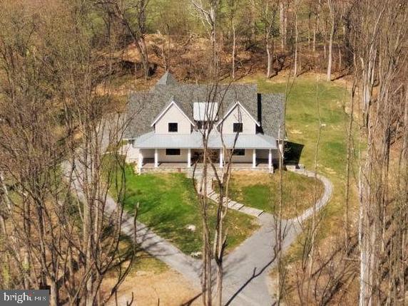 Modern Farmhouse Property in Beautiful Western Loudoun County

 MAJOR PRICE REDUCTION! NOW OFFERED AT $1,899,000

OVER $200K OF UPGRADES SINCE ORIGINAL PURCHASE!

This exceptional Nearly New Custom Home offers refined luxury and privacy on an elevated 5.2-acre wooded homesite bordered by protected Open Space and Stoneleigh Golf & Country Club. The setting is peaceful and scenic, with seasonal mountain views, mature trees, and a tranquil creek. NEW LANDSCAPING JUST INSTALLED.  Located just 1/2 mile from Round Hill and minutes to Route 7, the property provides both seclusion and convenience, along with no HOA, underground utilities, and high-speed Verizon Fios.
A private quarter-mile driveway leads to the stone and Hardi-Plank exterior, where the wraparound porch and curated hardscaping create a striking arrival. Inside, the home features 10-ft ceilings on the main floor and 9-ft ceilings on the upper level and basement, along with White Oak wide-plank wood floors, soaring beamed accents, a dramatic floor-to-ceiling stone gas fireplace, and a formal library with French doors. Large windows and an open layout highlight the natural surroundings and create a warm, elevated atmosphere and lovely views from every room.
The main-level Owner's suite offers a luxurious retreat with a custom closet including an island and window seat, a spa bath with heated floors, oversized walk-in shower, soaking tub, and toilet closet. Direct access to a covered porch with a gas fireplace extends the suite into a year-round outdoor living space.
The chef's kitchen is equipped with a Wolf range, Subzero refrigerator, Bosch dishwashers, Designer Level 5 Granite island, ceiling-height cabinetry with lighted glass uppers, walk-in pantry, and Butler's pantry. The main level also includes an open elegant dining area, a corner pocket office, the Great Room with Stone Gas Fireplace that leads to the rear covered porch, a full tiled bath and walk-in shower, and a mudroom/laundry with built-ins and access to the 3-car garage.
Upstairs offers a loft and media area with a wet bar and beverage fridge, plus three bedrooms-one ensuite and an additional full hall bath, which can be shared by loft area visitors and the two extra bedrooms.
The fully finished basement features high ceilings and includes a fifth ensuite bedroom, a hobby room with workbench, a large family room with an entertainment bar and full-size refrigerator, and a walkout to the custom patio and hardscape path to guest parking.
Premium upgrades include custom built-ins, designer window shades, High-End Systems, deluxe appliance and paint packages, upgraded blown-in insulation, 8 Ceiling Fans, a 500 GAL buried propane tank, and a whole-house generator. Close to Purcellville, Leesburg, wineries, breweries, parks, pools, and shopping, with Dulles Airport approximately 35 minutes away.

Current school district includes Woodgrove High School, Harmony Middle School, Mountain View Elementary. Check for updates, as districts change occasionally.