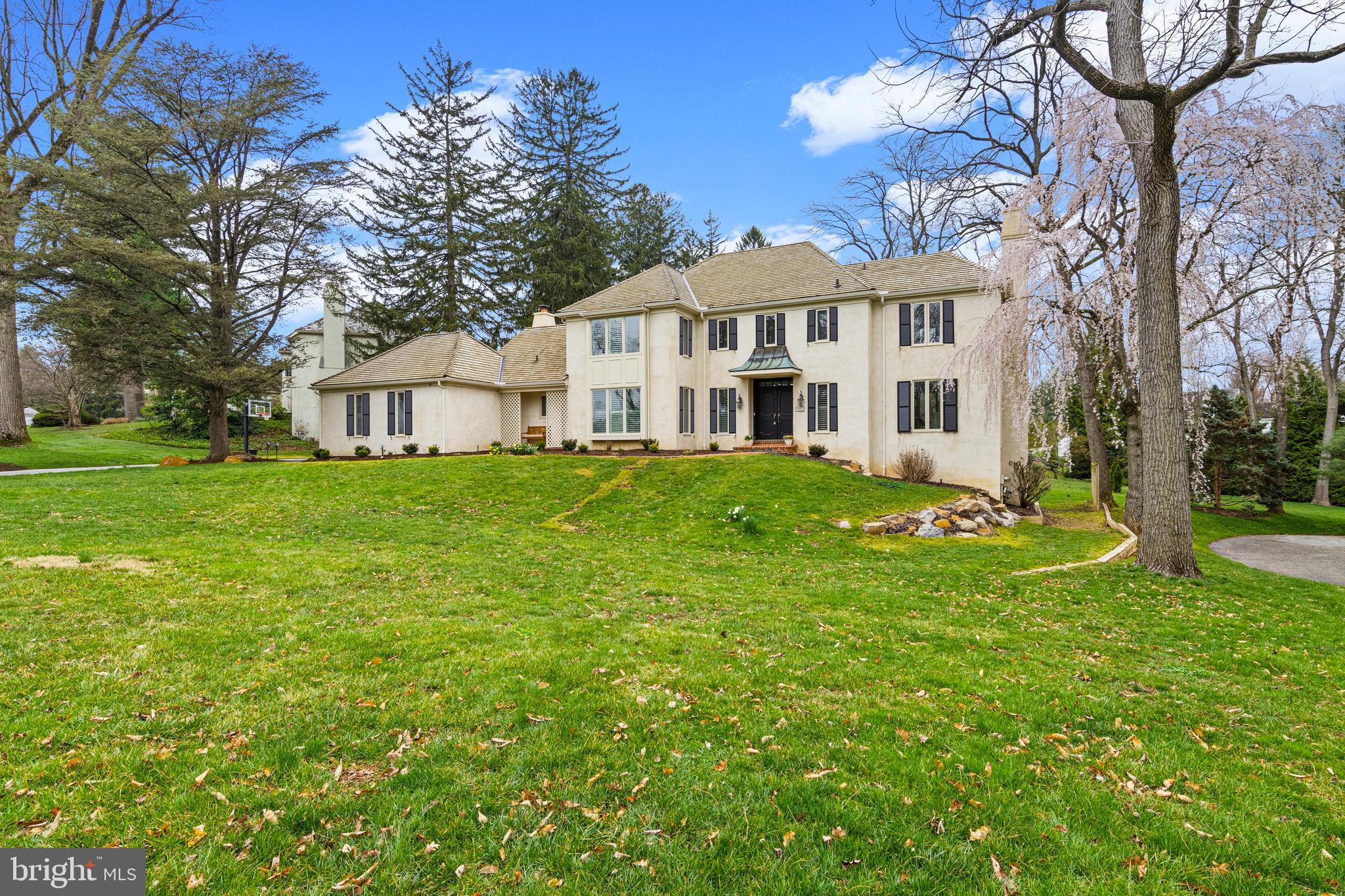 Nestled in the highly coveted Ravenscliff neighborhood of Radnor Township, within the top-ranked Radnor School District, this elegant 4-bedroom Colonial offers a rare combination of timeless design and modern comfort. Set on a private, expansive 0.8-acre lot—one of the largest in the community—this exceptional property provides both space and serenity. The home’s exterior has been thoughtfully refreshed with all new wood shutters and a newly resurfaced driveway, enhancing its already impressive curb appeal. A grand two-story foyer welcomes you into a light-filled interior featuring 9-foot ceilings, oversized windows, and refined architectural details throughout, including bay windows with deep sills and plantation shutters in many rooms. The thoughtfully designed main level includes a sophisticated step-down living room with a wood-burning fireplace, a formal dining room with direct access to the deck, and a private office complete with built-ins,  a fireplace, wet bar, and tranquil views. At the heart of the home is the expansive gourmet kitchen, outfitted with custom cabinetry, granite countertops, stainless steel appliances, and a center island with seating. It opens seamlessly to the breakfast area and a stunning two-story family room with a vaulted ceiling and a third wood-burning fireplace, creating a warm and inviting gathering space. A sliding door with side panels leads to a multi-tiered deck with a charming gazebo—perfect for entertaining or relaxing while overlooking the private backyard. Additional main-level highlights include a newly renovated mudroom/laundry area—an exceptional transition space—featuring extensive cabinetry, built-in lockers, a second refrigerator, quartz countertops, and direct access to the two-car garage. Upstairs, the spacious primary suite features two walk-in closets and a luxurious en-suite bath with dual vanities, a soaking tub, frameless glass shower, and private water closet. Three additional generously sized bedrooms share a well-appointed hall bath. The finished walk-out lower level provides flexible living space, complete with a full bath, recreation area, and access to a private patio. Special features include three fireplaces, a wet bar, plantation shutters, and a new top-of-the-line wireless security system. Recent updates include a cedar shake roof (8 years), central air (3 years), and a clean stucco inspection (2020), offering added peace of mind. As a member of the Ravenscliff community, you can enjoy access to the beautiful ponds, streams and walking trails in the neighborhood. Ideally located just minutes from downtown Wayne, with convenient access to fine dining, shopping, major highways, Center City Philadelphia, and Philadelphia International Airport, this home delivers the perfect blend of luxury, convenience, and everyday living in one of Radnor Township’s most desirable communities.