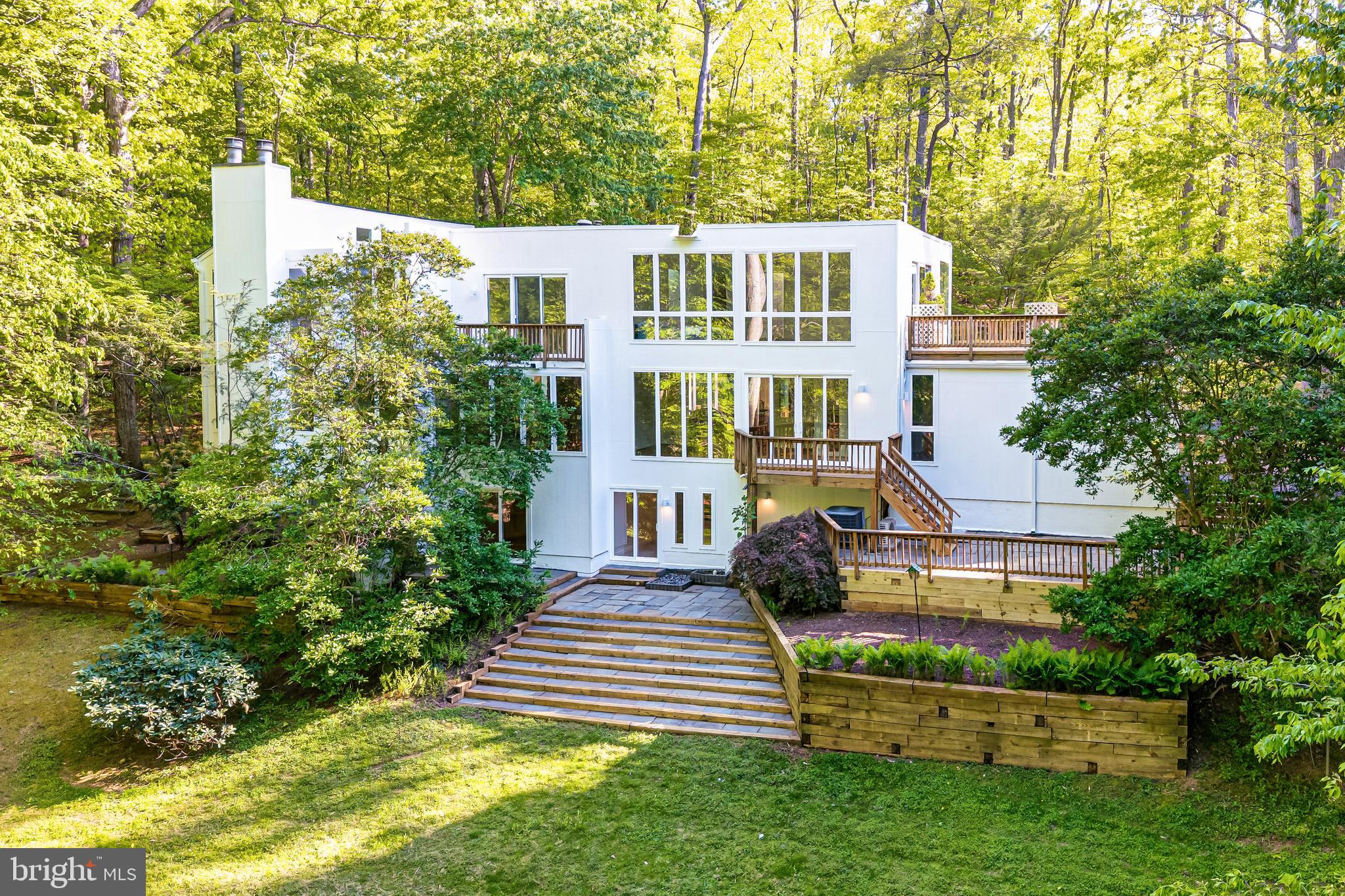Welcome to 125 Eagles Mere Road, a striking contemporary residence offering 5 bedrooms, 5 full baths, and 1 half bath, set within a private Great Falls setting. Thoughtfully updated with new Pella windows and doors, Hardie Board siding, refinished wood flooring, and a renovated primary bath, the home presents a well-composed layout designed to capture its natural surroundings while supporting both everyday living and entertaining.  

Inside, the main level unfolds with a series of connected living spaces defined by scale, light, and architectural detail. A two-story open staircase foyer introduces the home with a wall of windows. The living room offers an intimate gathering space with a wood-burning fireplace. The family room features a stone-faced fireplace with a beamed ceiling. The kitchen is designed for both function and gathering, featuring granite countertops, a full-height tile backsplash, oak cabinetry, and a center island with seating. The adjacent breakfast area is framed by skylights and windows, creating a bright and open setting, while the sunroom offers additional access to the deck and outdoor spaces. A main-level bedroom with en-suite bath and a private entrance from the deck provides flexibility for guests or single-level living.  

Upstairs, the spa-inspired primary suite serves as a peaceful sanctuary, bringing the outdoors in through floor-to-ceiling windows and a spacious rooftop deck. The renovated primary bath features a custom dual-sink vanity, a soaking tub overlooking the trees, and a walk-in shower. Abundant windows and skylights fill the space with natural light, creating a serene, nature-filled setting. The suite is complete with a seating area and a walk-in closet. 

Additional bedrooms are thoughtfully arranged to accommodate a variety of living needs, including one with an en-suite bath and another with its own fireplace, while a full hall bath serves the remaining rooms. 

The lower level expands the home’s versatility with an exercise room, media room, recreation room, and full bath, along with multiple walk-out access points to the patio and backyard. These spaces provide options for entertainment, fitness, or additional living needs while supporting the home’s overall functionality.  

Easy indoor-outdoor living is integrated throughout the property, with resealed decks on all sides of the home, multiple patio areas, and a layout that connects to the surrounding landscape bordering Potomac River regional parkland. Additional updates include new exterior lighting and gutters, enhancing both the home’s presentation and maintenance.  

Located within the Langley High School pyramid and close by to Great Falls Village, Riverbend Park, Potomac River trails, and major commuter routes, the home offers convenient access to Tysons, Reston, and the surrounding region while maintaining a private residential setting.  

This is a home designed for both everyday living and gathering, where space, light, and setting come together in a cohesive and well-executed design.