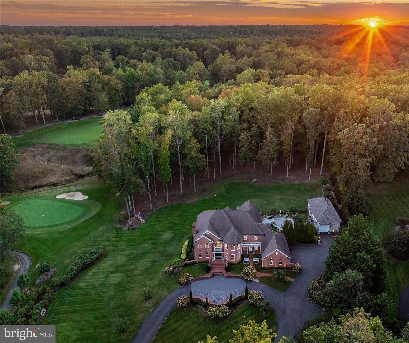 A showpiece estate offering the rare combination of grand scale, modern upgrades, complete privacy, and resort-inspired outdoor living. Set behind a private automated gate on nearly 3 acres, this solid brick estate offers nearly 10,000 sq ft fin. space inc. a detached garage, blending resort-style living, privacy, & modern-meets-classic design. Since 2019, the home has undergone an extensive renovation, inc. plumbing, electrical, UV-protected windows, and a 3-level double door French Style elevator. A newly expanded circular paver driveway & walkways—illuminated by handmade lanterns & low-voltage lighting—wind through curated grounds featuring a "white and pastel" floral palette, a cascading waterfall pond, and a private  750-ft wooded walking trail & "bird-watching sanctuary". A dramatic 2-story, sun-filled foyer welcomes you, highlighted by a Schonbek chandelier, a custom double front door, & a sweeping curved staircase. Distressed maple floors & exceptional artisan-crafted millwork create a sense of cohesion & craftsmanship throughout the home. The main level unfolds with beautifully appointed living spaces designed for both elegant entertaining & everyday comfort. A formal parlor w/ a fireplace offers a refined gathering space, while an artisan-crafted, richly paneled library features a coffered ceiling, a Napoleon Style lighting fixture, & a stately built-in desk. The private dining room is enclosed by a custom metal & glass wall w/double doors, creating an intimate yet dramatic setting for hosting dinners for 12+  guests. The family room—featuring pocket doors & surround sound—is anchored by a striking marble fireplace. It flows seamlessly into the kitchen & opens to private stone balconies, beautifully blending indoor and outdoor living. The chef’s kitchen is both sophisticated and functional, featuring a large central island, premium stainless-steel appliances by Viking and Sub-Zero, a warming drawer, integrated specialty appliances, and 2 climate-controlled walk-in pantries. The sunroom is the most beloved space in the residence. With soaring cathedral ceilings, a dramatic 72-inch linear steel fireplace, & panoramic views of the fairway, it offers an extraordinary retreat. Completing the main level-a spacious mudroom & 2 elegant half-baths, including a distinctive powder room finished w/Belgium blue stone flooring. The French Style 3-floor elevator leads to the upper level featuring 4 spacious bedrooms & three full baths. Enjoy the primary suite, w/a sitting room, double-sided fireplace, oversized closets, & a spa bath w/ marble, mosaic tile, steam shower, &  Schonbek lighting (laundry hookups in-suite). 2 additional bedrooms share a Jack & Jill bath w/stamped marble floors, while the 4th guest suite has a private luxe jacuzzi bath. The walk-out lower level includes a family room w/a fireplace, an executive office w/custom woodwork &  dedicated mini split HVAC, a private guest suite w/ a rainfall shower, & a fitness room w/ a sauna & red-light therapy. It is anchored by a custom mahogany bar w/ black granite flooring, a tap pump, 200+ bottle wine storage, & a kitchenette area. This level features LED-lit steps, Coretec flooring, a large covered stone patio ideal for outdoor gatherings, a spectacular laundry center, specialized utility rooms, and 2023 custom-cabinetry storage. The home offers unparalleled infrastructure: a 2019 well with 3 HP pump, dual Generac generators, four HVAC systems with five zones and mini-splits, instant-hot water, and a certified CertainTeed Presidential roof. A 2024 AV rack seamlessly controls Sonos, Lutron, and battery-backed Ubiquiti Wi-Fi. The 2,000 sq. ft. (est) detached stone building, boasts soaring bays, a cargo lift, EV charging, and natural stone detailing—a collector’s dream for cars, boats, or hobbies. Resort-style amenities: pools, tennis/pickleball, playground, walking paths & picnic area.