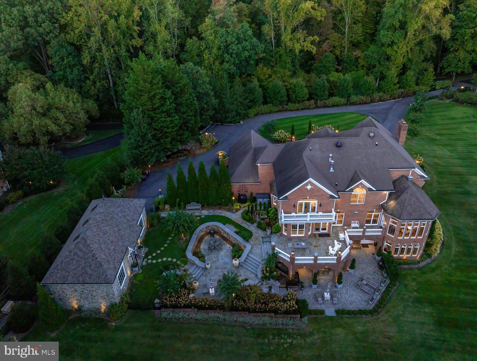 Enjoy this private gated golf estate offering rare seclusion, elegance, and a nature-rich backyard sanctuary designed for effortless multi-level entertaining. Set behind a private automated gate on nearly 3 acres, this solid brick estate offers nearly 10,000 sq ft fin. space inc. a detached garage, blending resort-style living, privacy, & modern-meets-classic design. Since 2019, the home has undergone an extensive renovation, inc. plumbing, electrical, UV-protected windows, and a 3-level double door French Style elevator. A newly expanded circular paver driveway & walkways—illuminated by handmade lanterns & low-voltage lighting—wind through curated grounds featuring a "white and pastel" floral palette, a cascading waterfall pond, and a private  750-ft wooded walking trail & "bird-watching sanctuary". A dramatic 2-story, sun-filled foyer welcomes you, highlighted by a Schonbek chandelier, a custom double front door, & a sweeping curved staircase. Distressed maple floors & exceptional artisan-crafted millwork create a sense of cohesion & craftsmanship throughout the home. The main level unfolds with beautifully appointed living spaces designed for both elegant entertaining & everyday comfort. A formal parlor w/ a fireplace offers a refined gathering space, while an artisan-crafted, richly paneled library features a coffered ceiling, a Napoleon Style lighting fixture, & a stately built-in desk. The private dining room is enclosed by a custom metal & glass wall w/double doors, creating an intimate yet dramatic setting for hosting dinners for 12+  guests. The family room—featuring pocket doors & surround sound—is anchored by a striking marble fireplace. It flows seamlessly into the kitchen & opens to private stone balconies, beautifully blending indoor and outdoor living. The chef’s kitchen is both sophisticated and functional, featuring a large central island, premium stainless-steel appliances by Viking and Sub-Zero, a warming drawer, integrated specialty appliances, and 2 climate-controlled walk-in pantries. The sunroom is the most beloved space in the residence. With soaring cathedral ceilings, a dramatic 72-inch linear steel fireplace, & panoramic views of the fairway, it offers an extraordinary retreat. Completing the main level-a spacious mudroom & 2 elegant half-baths, including a distinctive powder room finished w/Belgium blue stone flooring. The French Style 3-floor elevator leads to the upper level featuring 4 spacious bedrooms & three full baths. Enjoy the primary suite, w/a sitting room, double-sided fireplace, oversized closets, & a spa bath w/ marble, mosaic tile, steam shower, &  Schonbek lighting (laundry hookups in-suite). 2 additional bedrooms share a Jack & Jill bath w/stamped marble floors, while the 4th guest suite has a private luxe jacuzzi bath. The walk-out lower level includes a family room w/a fireplace, an executive office w/custom woodwork &  dedicated mini split HVAC, a private guest suite w/ a rainfall shower, & a fitness room w/ a sauna & red-light therapy. It is anchored by a custom mahogany bar w/ black granite flooring, a tap pump, 200+ bottle wine storage, & a kitchenette area. This level features LED-lit steps, Coretec flooring, a large covered stone patio ideal for outdoor gatherings, a spectacular laundry center, specialized utility rooms, and 2023 custom-cabinetry storage. The home offers unparalleled infrastructure: a 2019 well with 3 HP pump, dual Generac generators, four HVAC systems with five zones and mini-splits, instant-hot water, and a certified CertainTeed Presidential roof. A 2024 AV rack seamlessly controls Sonos, Lutron, and battery-backed Ubiquiti Wi-Fi. The 2,000 sq. ft. (est) detached stone building, boasts soaring bays, a cargo lift, EV charging, and natural stone detailing—a collector’s dream for cars, boats, or hobbies. Resort-style amenities: pools, tennis/pickleball, playground, walking paths & picnic area.