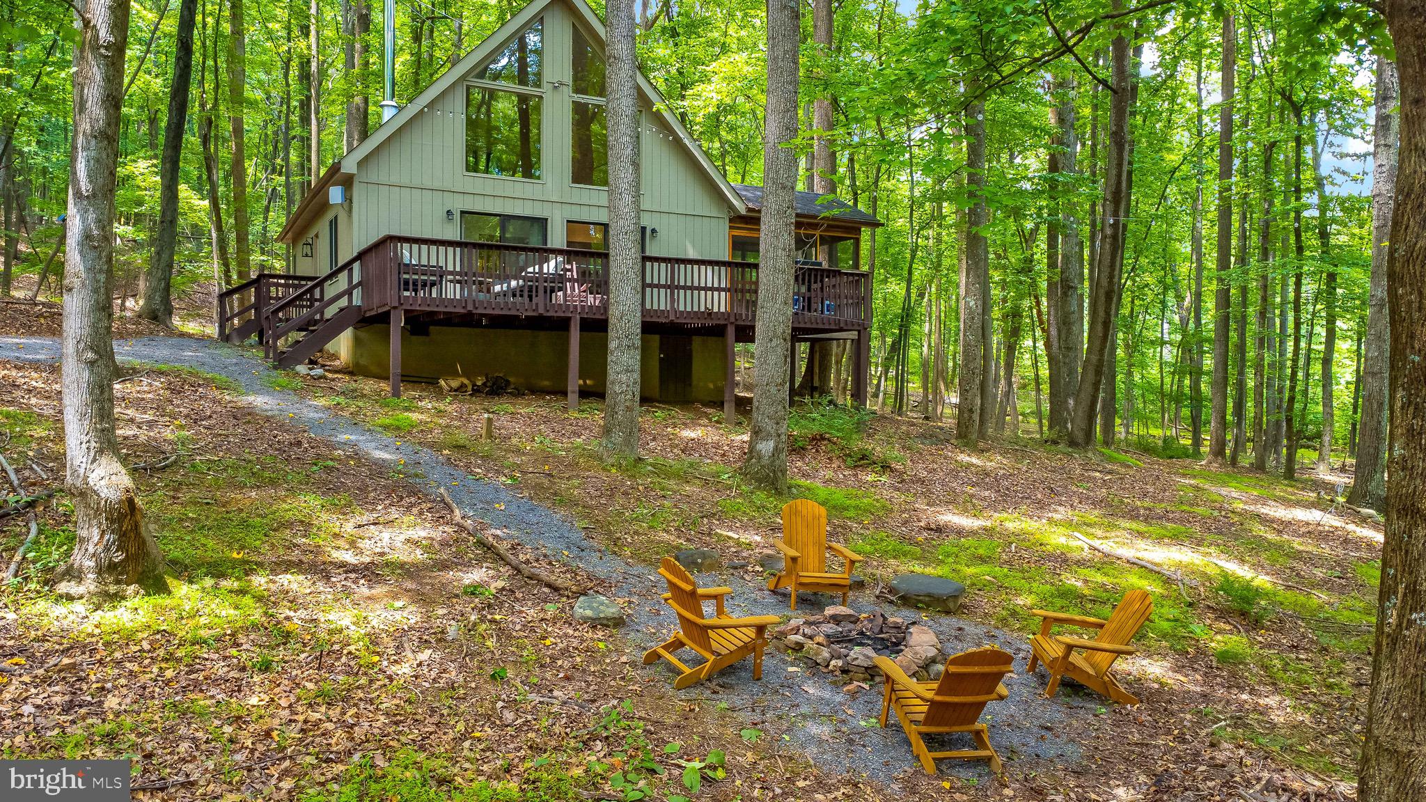 Tranquility at its finest! At the end of a quiet lane, sits this serene 3 bedroom home on over 5 private wooded acres. Currently ran as a successful AirBNB, full time living will feel like a vacation every day. Most contents convey, giving the home a magazine appearance and spa like retreat feel--- the only thing you need to bring are your personal belongings. The main floor spreads LVP throughout the open concept of kitchen, dining, and living area. With doors on 3 sides of the home, nature awaits at nearly every step. From the dining area, you can access a cozy covered screened porch to utilize in almost any weather. From there or sliding doors from the living room, you can access the expansive open deck that stretches the full length of the front of the house. The main floor houses the full bath, centrally located between all living areas. Downstairs in the right bedroom, there is a full size nearly new stacked washer and dryer that also conveys! Upstairs in the loft is the largest of the 3 bedrooms, with an amazing view of the gorgeous woods through your vaulted window wall. With thousands of dollars worth of fabulous furniture, decor, and home items conveying at no additional cost, you will be set to walk in to your new home with no stress!!!