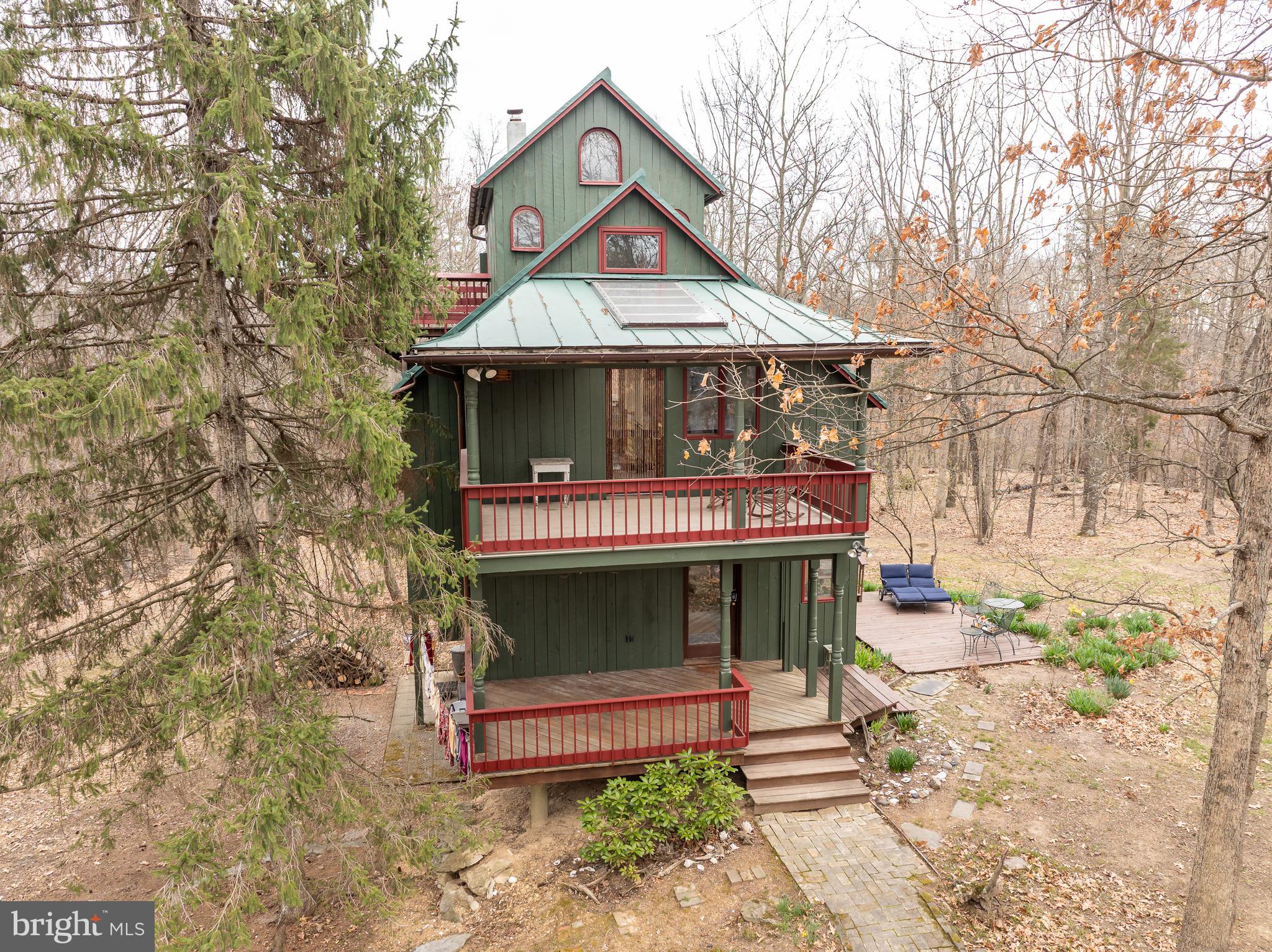 A very unique custom-built home nestled in the woods. 3 bedrooms, 1.5 baths.  Kitchen has custom built cabinets. Hardwood floors throughout. 2 bedrooms on upper floor, one bedroom on the upper 2nd floor.  Laundry rm and family rm in basement. Large windows and skylights for lighting and warmth. Furnace has a humidifier. 2 car detached garage with a workshop attached to it. 4.06 acreage, 2.02 of the acreage is deeded separately. It's possible to build another home on the 2.02 acres. Well hydrant by garage. Driveway has a gate. Home has 2 porches, 3 decks and 1 patio.  No active HOA. There is a 2.57- additional lot available to purchase WVBE2038724.