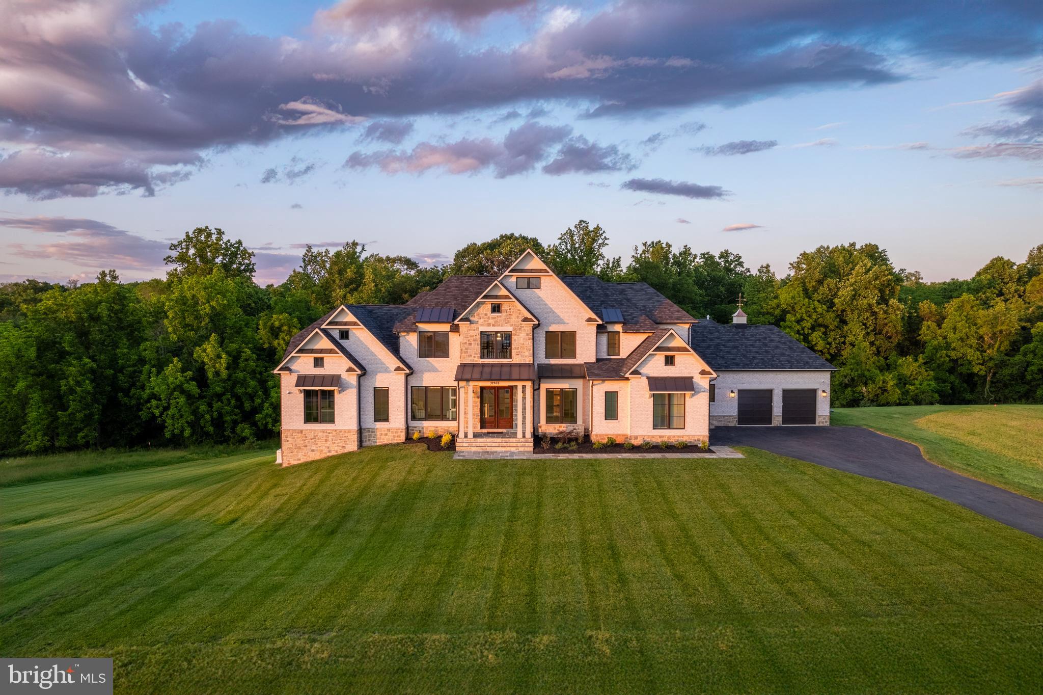 Welcome to an unparalleled experience of luxury living in the prestigious Banbury Cross community, nestled in the heart of Middleburg's horse and hunt country. This brand-new construction, never lived in, offers the rare advantage of immediate occupancy, bypassing the lengthy wait for new builds.

Situated on a premium 3.6-acre lot, this estate backs onto serene woods and a picturesque creek, presenting breathtaking views of farmland and the majestic Blue Ridge Mountains. The all-brick and stone exterior, enhanced with premium stone on all four sides, exudes timeless elegance and durability. A brand-new full home generator ensures uninterrupted comfort.

Inside, luxury and convenience abound. The three-floor elevator lift ensures seamless access to every level of this exquisite home. At the heart of the home, the kitchen is a chef's dream, featuring a Wolf/Sub-Zero appliance package, an upgraded glass wine refrigerator, Omega cabinetry, and a spacious 12-foot island. Adjacent to the kitchen, the family room boasts a stunning coffered ceiling and a floor-to-ceiling stone fireplace, creating a warm and inviting atmosphere. The seamless transition to the extended rear deck, constructed with long-lasting Trex planks and upgraded railings, provides an ideal space for outdoor gatherings and offers stunning natural vistas.

The first-floor primary suite is a haven of comfort, featuring wide-planked hardwood floors, two expansive walk-in closets with custom cabinetry, and a lavish en-suite bathroom. An in-law suite on the first floor, complete with a beautiful bathroom, walk-in closet, and deck access, offers private accommodation for guests.

The lower level is designed for entertainment and wellness, featuring a gym with a full wall mirror and rubber flooring, built-in cabinetry in the office, and a large safe for valuables.

Two fully insulated garages cater to the automobile enthusiast, featuring newly installed cabinets, slat wall garage systems, and epoxy floors. The front two-car garage is equipped with a Tesla charger, while the rear garage boasts a Mitsubishi mini-split AC/heat unit and two hydraulic car lifts, accommodating up to four cars in total.

State-of-the-art amenities include premium lighting throughout, a full house central vacuum system encompassing even the garages, and two strategically placed laundry rooms on the first and second floors. A full house water softening system, reverse osmosis water system in the kitchen beverage center, and additional beverage refrigerators in the lower-level rec room and butler’s pantry elevate the living experience. Privacy blinds throughout the house ensure a sense of seclusion and tranquility. Advanced interior/exterior audio/video/security systems and home automation offer peace of mind and convenience, while lightning-fast internet keeps you connected.

This exquisite property represents the pinnacle of modern luxury, offering a seamless blend of sophisticated design, premium upgrades, and unparalleled comfort. Discover your new home where every detail has been thoughtfully curated to provide an extraordinary living experience. Welcome to a new level of luxury and elegance in your dream home!