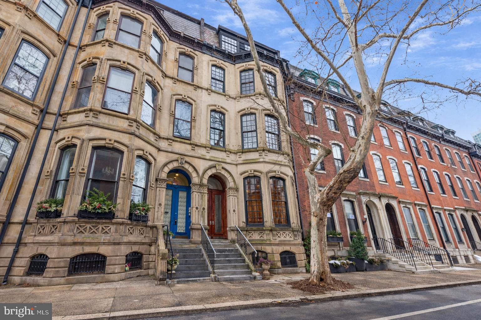 Situated on one of the most beautiful blocks in Rittenhouse Square, 2106 Spruce Street rarely offered 22 foot wide by 150 foot deep lot allowing up to 4 car parking and a private garden, with 14 foot ceiling this Frank Furness designed masterpiece exemplifies the elegance, artistry, and enduring craftsmanship of 19th-century Philadelphia architecture. Circa 1871, this, 6-bedroom, 5.5-bathroom residence spans four floors above ground plus a finished lower level, offering over 5,000 square feet of refined living space with an elevator. Behind the ornate stone façade and marble stoop, double wooden doors open to a grand vestibule and entry hall where 14-foot ceilings, intricate crown molding, original hardwood floors, and signature Furness arches showcase timeless craftsmanship. The light-filled living room is anchored by oversized bay windows. Down the hall you’ll find the chef’s kitchen equipped with stainless steel countertops, Sub-Zero refrigeration, Dacor range with Broan hood, double ovens, and a center island, along with a dining nook, powder room, elevator access, and hallway storage. Beyond lies a formal dining room framed by windows on two sides with recessed lighting and access to a rear deck overlooking an expansive slate patio oasis and rare two-car garage with access from Cypress street. Ascending the original staircase, the second floor hosts the primary suite, an elegant retreat with windows on two exposures, and a spa-like bath with dual vanities, a mirrored wall, private water closet, and oversized glass shower with a built-in bench. A large walk-in closet with lockable drawers and custom millwork completes the primary. The front bedroom on this level features grand French doors beneath a circular transom window, built-in shelving, and classic bay windows that flood the room with light. The third floor offers two additional bedrooms, each with bay windows, generous closets, and en-suite baths. The rear bedroom features light from two exposures, double closets, and a fully tiled bath with a linen closet and subway-tile surround. The front bedroom includes recessed lighting, a cedar closet, and a vintage bath with an enclosed tub/shower combination. The fourth floor adds two more bright and generously sized bedrooms, one with large industrial-style windows and built-in shelving, plus a full hallway bath with storage vanity and tub/shower combo. The finished lower level provides a private guest or au pair suite, complete with its own kitchenette, bathroom, bedroom, laundry area, and separate rear access, along with abundant storage. Blending historic Frank Furness architecture, grand proportions, and modern comfort, 2106 Spruce Street is a true Rittenhouse Square treasure, a timeless residence masterfully preserved and thoughtfully updated, offering elegant living just steps from the city’s premier dining, shopping, and cultural landmarks.