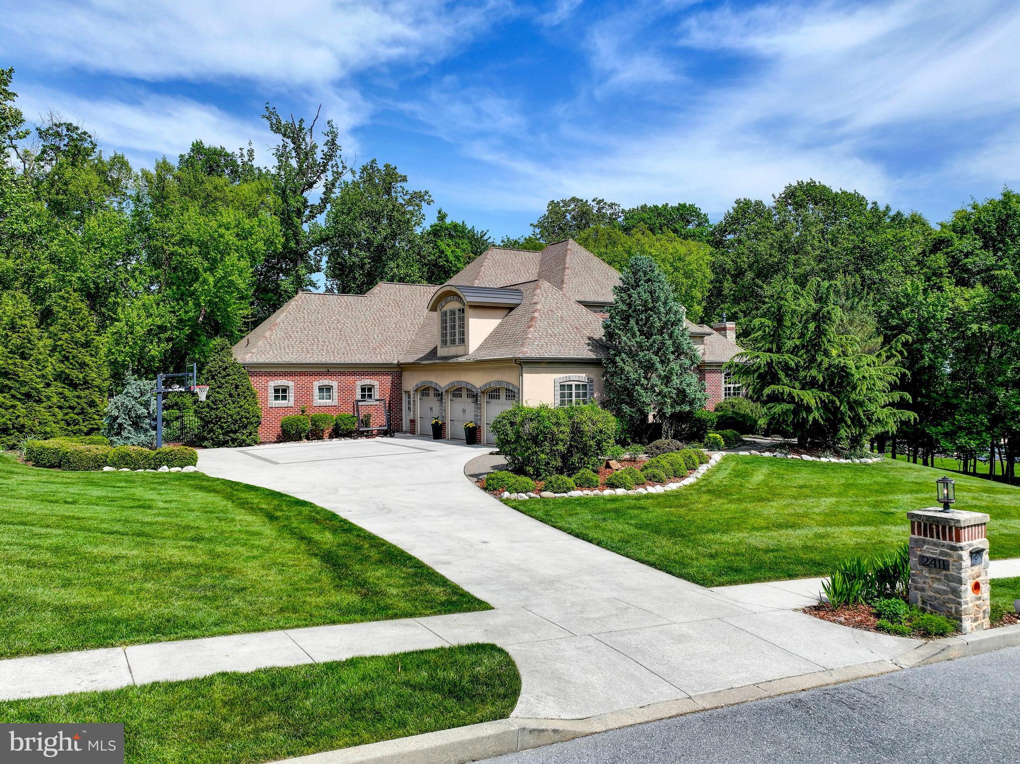 Nestled in the prestigious Estates of Forest Hills, this incredible and timeless custom home by Roland Builders offers exceptional craftsmanship, luxury finishes, and stunning architectural detail throughout. The striking brick and stone exterior, unique rooflines, and oversized windows create unmatched curb appeal and make this residence truly one of a kind.

Inside, gleaming hardwood floors, soaring 10-foot ceilings on the main level, and 9-foot ceilings upstairs enhance the home’s spacious and elegant design. A dramatic two-story foyer welcomes you, complemented by both front and rear staircases for convenience and functionality. The thoughtfully designed floor plan includes a private first-floor office, formal living room with fireplace, and elegant formal dining room ideal for entertaining.

The luxurious main-level primary suite is a true retreat, featuring vaulted ceilings, an expansive walk-in closet, a spa-inspired bath with dual-entry shower, vertical spa features, soaking tub, and its own cozy gas fireplace. A second bedroom suite is also conveniently located on the main level, offering ideal accommodations for guests or multigenerational living. The chef’s kitchen is appointed with granite countertops, gas cooking, stainless steel appliances, and opens seamlessly to the family living spaces.

Offering 5 bedrooms and 5.5 beautifully appointed bathrooms, this exceptional home provides generous living space throughout. The expansive finished walk-out lower level offers incredible flexibility with a full bath, gym area, and abundant recreation and entertaining space with direct access to the side yard.

Situated on a professionally landscaped one-acre plus homesite with a fenced rear yard, the outdoor living spaces are truly extraordinary. Enjoy a resort-style backyard complete with a custom hot tub, pool pergola, wood-burning fireplace, and extensive hardscaping designed for year-round entertaining and relaxation. This exceptional property blends timeless elegance, luxury amenities, and everyday comfort in one remarkable home.