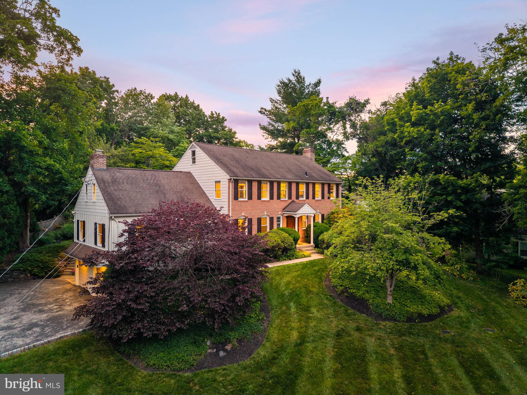 Nestled on a private court in Gladwyne, 1144 Norsam Road is a timeless brick Colonial that seamlessly blends traditional architecture with the comforts of modern living. Thoughtfully designed with gracious formal spaces, beautiful hardwood floors, abundant windows, well-positioned skylights, and exceptional indoor-outdoor flow, this five-bedroom, three-and-a-half-bath residence offers warmth, functionality, and an abundance of natural light. Set on a quiet cul-de-sac offering a cherished neighborhood experience, the property offers a rare blend of privacy, community, and everyday livability.

A welcoming center hall floor plan unfolds into elegant living spaces filled with natural light. The formal living room is anchored by a classic brick-lined fireplace and framed by oversized windows on three sides. The dining room features a wall of windows and French doors that open directly to the terrace and beautifully landscaped grounds beyond. A spacious private office offers the perfect balance of accessibility and quiet separation for work or study.

At the heart of the home is a sun-drenched eat-in kitchen designed for gathering. Ample counter space allows for multiple helping hands in the kitchen, while a large center island, generous dining area, extensive cabinetry, walk-in pantry, built-in desk space, skylight, and French door to the patio make the space equally suited for everyday living and large-scale entertaining. The adjoining breakfast and sitting areas are bathed in sunlight throughout the day. Just beyond, a spacious family room features charming built-ins, a raised-hearth fireplace, and an open, airy feel that naturally draws people together.

Upstairs, the primary suite offers a luxurious retreat with a tray ceiling, sun-filled walk-in closet, custom cherry built-ins, and a private en-suite bath. Three large additional bedrooms feature hardwood floors, abundant natural light, generous closet space, and access to a shared hall bath. A separate fifth bedroom with its own en-suite bath and private staircase provides ideal accommodations for guests, an au pair, or multigenerational living. An upstairs laundry room adds everyday convenience.

A practical rear entry with dramatic two-story ceilings and beautiful natural light includes mudroom space and an additional flexible room currently used as a gym, offering endless possibilities as a second office, expanded mudroom, hobby room, or creative workspace.

Outside, the home truly shines. A paver patio, accessible from both the kitchen and dining room, creates a seamless connection between indoor and outdoor living and provides the perfect setting for outdoor dining, entertaining, or gathering around a fire pit. The expansive lawn offers ample space for sports, games, and recreation, while mature landscaping delivers exceptional privacy and year-round beauty. Sweeping views from the second floor and proximity to Saunders Woods further enhance the property’s unique connection to nature.

Additional highlights include a new septic system installed by Gray Brothers in 2019, higher ceilings in select spaces including the kitchen and primary suite, abundant storage throughout, and a two-car garage.

Beyond the property itself, residents enjoy the rare charm of life on a true Gladwyne court—a quiet setting where you can ride bikes, neighbors gather for block parties, and through traffic is virtually nonexistent. Just moments from the village center, enjoy easy access to local favorites including McCaffrey’s, the library, coffee shops, pharmacy, post office, parks, country clubs, and the vibrant dining destinations of Conshohocken and throughout the Main Line. Beloved community traditions, from the Memorial Day Parade and Firehouse Halloween to Santa’s annual visit aboard a fire truck, create a sense of connection and community that is increasingly hard to find.