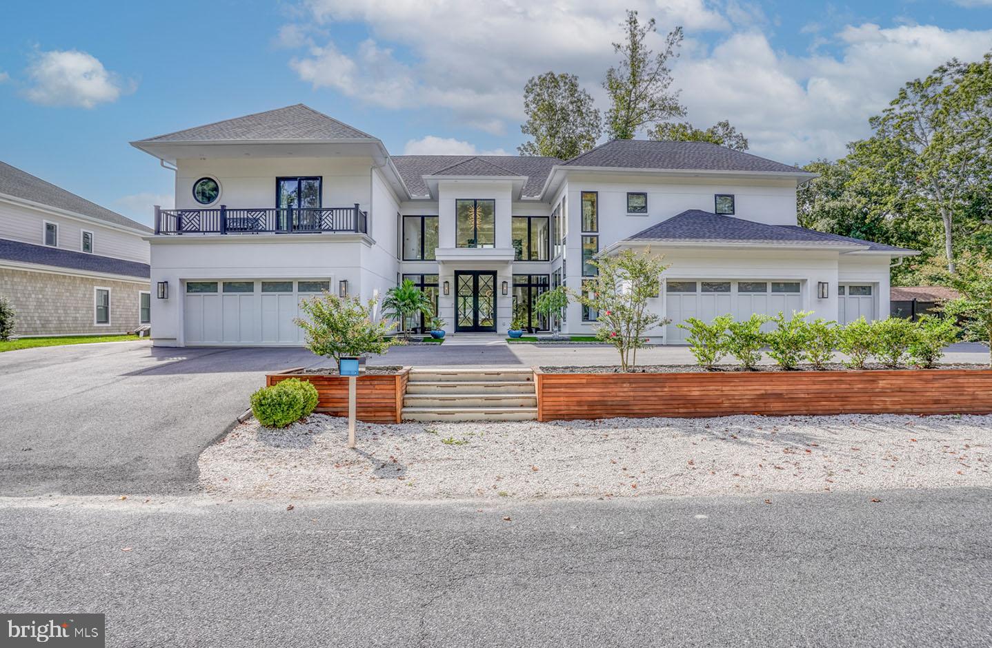 Location, location, location!  Welcome to this luxurious 5 car garage waterfront marvel at 104 W. Buckingham Dr., located in the coveted Rehoboth Beach Yacht and County Club. This sought-after Rehoboth Beach location is renowned for its beaches, diverse dining, minutes away from Tanger outlets and downtown shopping, and the entertainment night life that Dewey beach has to offer. This builder's personal home has modern sophistication with just over 7,000 square feet and is designed to take your breath away. Offering the ultimate amount of on and off-street parking, the craftsmanship shines in this vacation destination for people who dream big, love deeply, and live boldly. Set along Bald Eagle Lagoon, the house stands out among the rest boasting 2 deepwater slips for the Rehoboth Bay area. Offering one 20,000 lb boat lift, one wet boat slip, and two jet ski lifts it is truly a boater’s paradise.  The extra wide 6'x60' pier is decked with IPE decking for years of longevity.  Includes a 50 AMP power post with electric and fresh water on the dock.  The landscape lights and dock lights show off the exterior in style and function.  The spectacular fiberglass saltwater plunge pool is equipped with a waterfall and fire feature along with 3 outdoor showers, 2 of which are private and one down by the dock for a quick rinse after enjoying your day on the water.  The exterior decks on both floors have teak covered porches that allow you to have multiple areas to entertain and relax. An extra-large gas firepit on a paver gathering space delights guests for hours of waterfront conversation under the stars. With an open-air kitchen and a gas and EVO grill, your guests will enjoy fresco dining, laughter and unforgettable gatherings. Dazzling you upon arrival with its 2 exterior fire waterfall features and gas lighting it leads you to a spectacular mahogany front door.  Once inside you are greeted with 20'+ tall ceilings with a tiled foyer and exquisite lighting features and hardwood floors throughout the home. Step into the gourmet kitchen, where every detail is crafted for those who love to cook and entertain.  Adorned with quartz and Bertazzoni appliances and a walk-in pantry with additional prep space and second full size refrigerator this kitchen is the showpiece of this amazing house.  Views of the canal can be seen through the massive, fixed windows and double opening sliding doors in the back of the home.  A wood-burning limestone fireplace in one of the family rooms that overlook the bay makes for an extra cozy space on those cold nights. With a total of 4 living room areas, each equipped with large screen TVs allows owners and guests to each have a room to come home and unwind.  For the dog lover in mind, this house also incorporates a laundry room downstairs with dog grooming bathtub station. Enjoy the lighted open glass railing staircase or take solace in the bright double window shafted elevator to the top floor where the upstairs boasts 4 large bedrooms with their own private bath.  Add the functionality of a kitchenette and 2 laundry rooms upstairs, along with a living area that has the view of the lagoon from the wrap around rear porch with glass railings, the views are unparalleled. It’s a place which transcends the typical home and caters to your utmost comfort and desire.