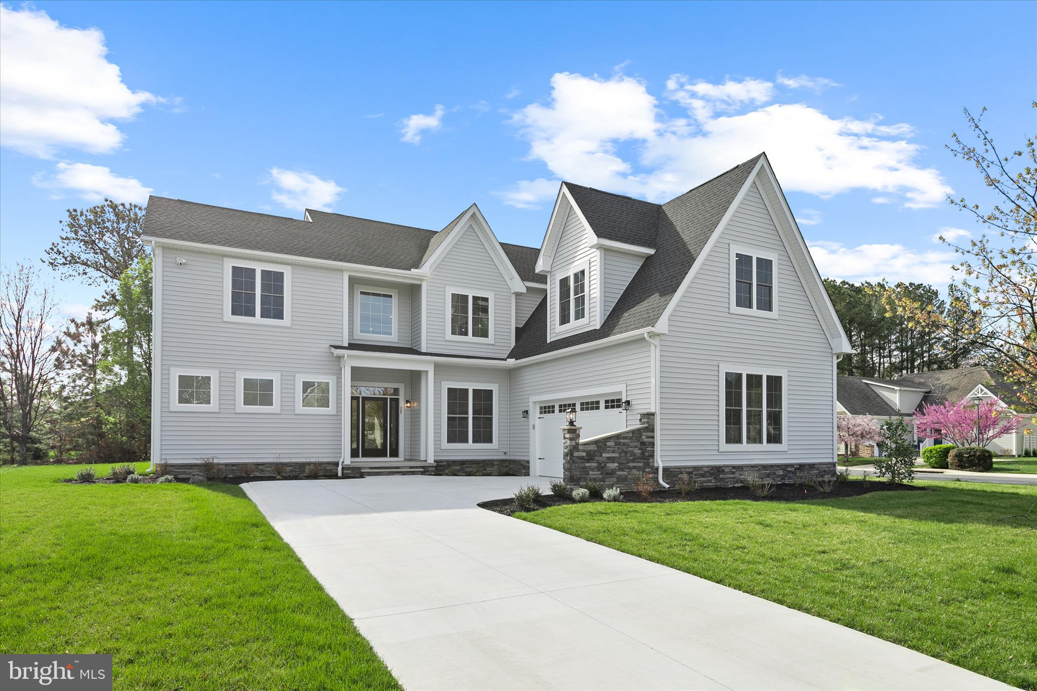 Introducing a stunning new construction home in the charming coastal town of Lewes, where modern design meets refined comfort. Nestled in a quiet neighborhood with mature trees and sidewalks, this home offers a peaceful setting just minutes from downtown, beaches, dining, and the ferry. A dramatic two-story foyer welcomes you inside, showcasing soaring ceilings, abundant natural light, and wide-plank luxury vinyl flooring that flows throughout the main level. To the right, a private office with French atrium doors and recessed lighting provides the perfect work-from-home space, while extra-tall doors throughout enhance the home’s elevated feel.

The great room is nothing short of breathtaking, with its soaring two-story ceilings, expansive windows, and a statement farmhouse-style ceiling fan that draws the eye upward. A sleek electric fireplace with custom built-in shelving creates a warm and inviting focal point. Here a wall of glass with extra-tall sliding doors opens to a screened porch, seamlessly blending indoor and outdoor living while overlooking a tranquil, tree-lined backyard

The gourmet kitchen is both stylish and functional, anchored by a large quartz island with seating, a black quartz sink, gooseneck faucet, built-in microwave, and beverage refrigerator. Crisp white 42-inch cabinetry with black hardware, display cabinets, a Lazy Susan, and deep drawers are paired with a quartz backsplash and high-end stainless steel Bosch appliances, including a gas range and refrigerator. Adjacent to the kitchen, a spacious dining area is enhanced by a sunlit bump-out, where an abundance of windows fills the space with natural light and creates an inviting setting for everyday meals and memorable gatherings. A sliding barn door opens to a spacious walk-in pantry with custom wood shelving and the laundry room featuring a quartz-topped sink, built-in platform for the washer and dryer, and a large window for natural light. A powder room with a quartz topped navy vanity and garage access completes the space.

The main-level primary suite is a private sanctuary, offering a luxurious retreat with vaulted ceilings, recessed lighting, its own electric fireplace, and a peaceful sitting area framed by large picture windows. The en suite bath is a true showpiece, featuring a multi-jetted freestanding soaking tub set beside its own fireplace, creating a spa-like ambiance. A sculptural chandelier adds an artistic focal point, while the expansive, level-entry walk-in shower showcases tile and stone accents, a frosted window for natural light, and sleek black fixtures. The oversized walk-in closet is outfitted with custom wood shelving, as are all closets throughout the home, reflecting a commitment to quality and organization.

 Ascending the elegant wood staircase with black iron balustrades, the upper level continues to impress. A versatile loft-style sitting area offers additional living space, while a full bath serves the upper level. One bedroom enjoys access to a nearby balcony, perfect for soaking in fresh air and views of the natural surroundings. Another spacious bedroom at the front of the home is currently styled as a fitness room, complete with rubber flooring and mounted fans for comfort during workouts. A full hall bath and a large unfinished walk-in storage room offer additional flexibility and potential. Additional features include a sprinkler system, custom closet shelving throughout, and a thoughtfully designed layout that blends style and function.

This remarkable home offers the opportunity to enjoy elevated coastal living in one of Delaware’s most desirable locations, where modern elegance meets the relaxed charm of the shore.