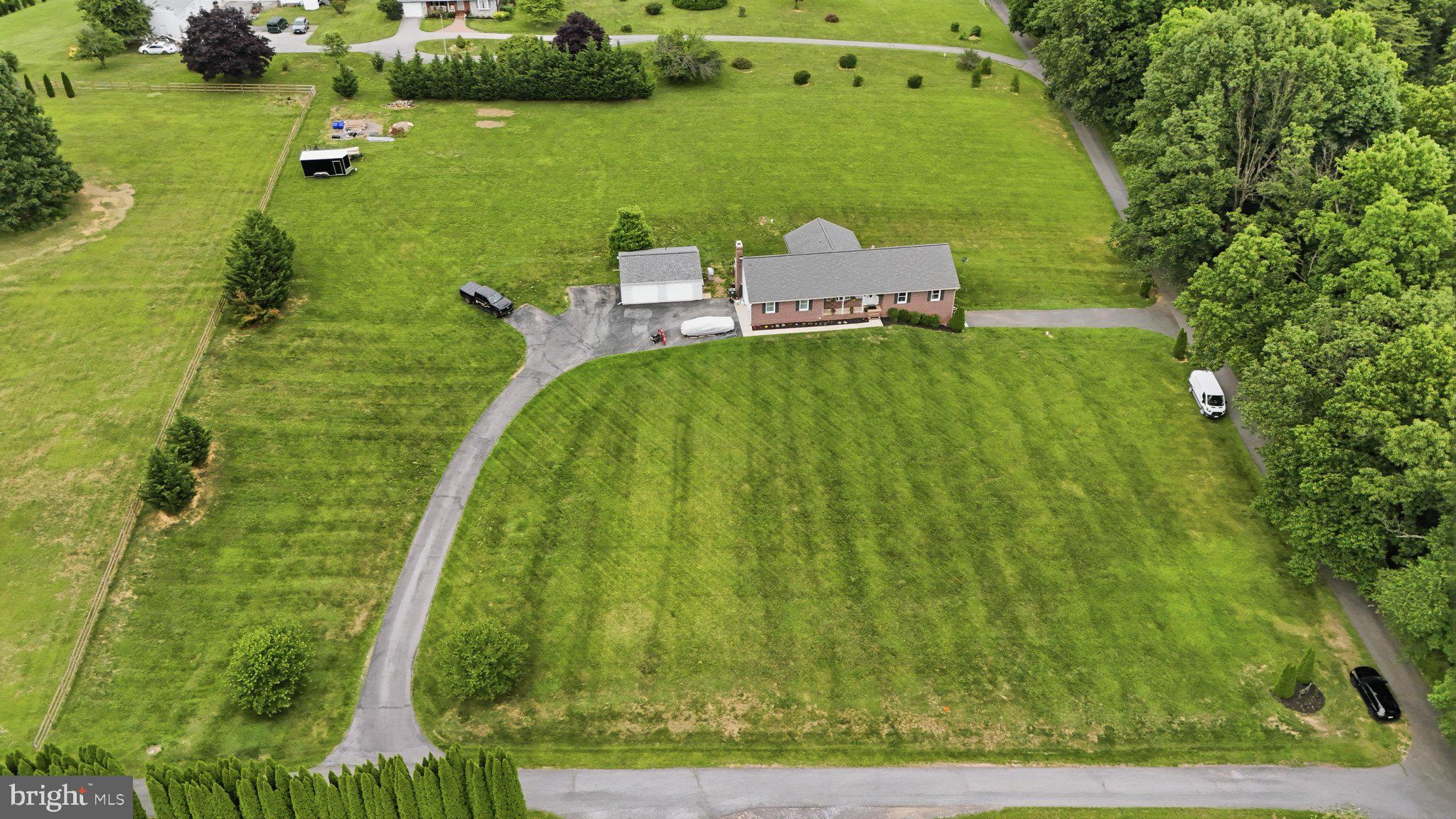 Rarely does a property offer this exceptional combination of space, privacy, versatility, and income potential. Situated on a picturesque and private 2.90-acre lot with no HOA, this beautifully maintained 4-bedroom, 4-full-bath Brick Rancher, built in 1991 and offering approximately 3,440 square feet of living space, provides the ease and convenience of first-floor living while offering thoughtfully designed flexible spaces throughout. Updated over the years, This exceptional home is ideal for buyers seeking accommodations for extended family, guests, or the opportunity for supplemental rental income with 2 In-Law Suites. The spacious main level features an oversized eat-in kitchen with granite countertops, a breakfast bar, new  tile flooring, and direct access to a large screened porch and expansive deck overlooking the peaceful setting. The inviting family room boasts vaulted ceilings, skylights, a stone wood  fireplace, and beautiful hardwood floors that continue into the living room, while the generous primary suite offers two closets, including a walk-in closet, and a beautifully updated private tile bath. Throughout the home, you'll appreciate the updated tile bathrooms, updated flooring, gleaming hardwood floors, recessed lighting, ceiling fans, walk in closets, oversized rooms, and abundant storage. The finished walk-out lower level features a full kitchen, full bathroom, separate entrance, and additional living space, creating exceptional flexibility for extended family, guests, or supplemental income potential. The detached garage has also been converted into a one-bedroom living area with its own septic system, 2 window ac units, full bath, kitchen and laundry, offering even more possibilities. Additional features include an active radon mitigation system, two electrical panels plus a subpanel, , sliding glass doors, all appliances conveying, and a septic system inspected approximately one month ago. Roof is approx 12 yrs,  H20 is 10 yrs.  200 + elec service 2 boxes. This is a truly rare opportunity to own a beautifully maintained home that combines the convenience of one-level living with exceptional flexibility, privacy, and endless possibilities in a serene setting. This is a must see !!