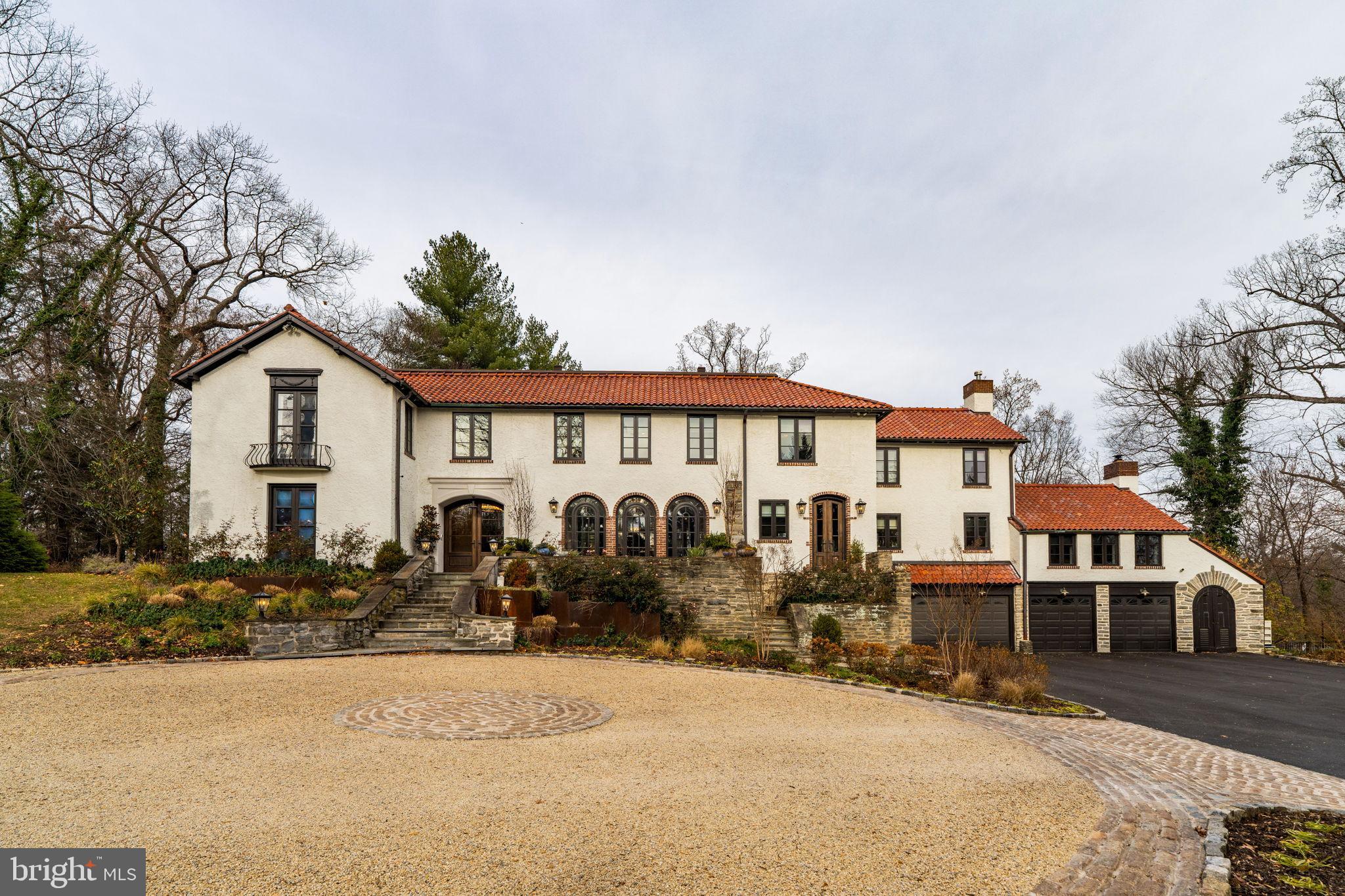 Privately set along a quiet lane in Northside Haverford, just moments from the historic Merion Cricket Club, this exceptional residence has been fully renovated with an unwavering focus on craftsmanship, materials, and architectural detail. The result is a home that honors its European-inspired heritage while seamlessly delivering refined modern luxury and everyday functionality.

A circular drive and stone approach lead to the striking stucco façade, clay tile roof, arched openings, and iron detailing. Inside, a dramatic, wide foyer with custom tile flooring and a grand double staircase creates an immediate architectural statement, offering both scale and symmetry rarely found.

The first floor unfolds into a series of beautifully defined and generously proportioned spaces. The formal living room features a fireplace and custom built-ins, while a sunlit first-floor office just beyond offers abundant natural light and exceptional functionality. The well-sized dining room, complete with a working fireplace, flows effortlessly into a front sunroom with a bar and direct porch access—ideal for entertaining or relaxed daily living.

At the heart of the home, the kitchen is both striking and highly functional. Stunning marble countertops, custom cabinetry, a statement Lacanche range, and a Sub-Zero refrigerator anchor the space. Large glass doors open directly to the rear patio and pool, creating seamless indoor-outdoor flow. A beautifully designed butler’s pantry provides exceptional storage, prep space, and support for entertaining.

Adjacent to the kitchen, the great room impresses with vaulted ceilings, exposed wood beams, a fireplace, and a nearby full bath, offering flexible use as a living space, guest area, or potential first-floor suite. Toward the rear, a true showstopper awaits—an extraordinary media and entertaining room with wood-beamed ceilings and a projector-screen television, perfectly designed for movie nights, game days, or large gatherings while opening to the terraces beyond.

Upstairs, the primary suite is privately situated and thoughtfully designed as a peaceful retreat. The bedroom features beautiful wood ceiling detailing, while the spa-inspired bath includes a freestanding soaking tub, oversized glass-enclosed shower, patterned tile floors, and custom vanities. A boutique-style dressing room with extensive custom cabinetry, integrated lighting, seating, and a stone-topped center island completes the suite.

Secondary bedrooms are spacious and well-appointed, complemented by a conveniently located second-floor laundry room and a dedicated workout or wellness space.

The finished lower level continues the home’s thoughtful design with a recreation area, custom mudroom, and a full bath featuring a second laundry and a shower ideal for a dog wash.

Outdoors, the property transforms into a private, resort-style retreat. Expansive stone terraces overlook a custom pool with raised spa, outdoor kitchen, and multiple seating and dining areas. Café lighting, terraced gardens, walking paths, and a tucked-away fire pit lounge create a serene, estate-like setting, while a gated entrance, fully fenced yard, mature landscaping, new irrigation system and wooded surroundings provide exceptional privacy.

A rare Northside Haverford offering defined by architectural integrity, extensive renovation, and exceptional indoor-outdoor living.