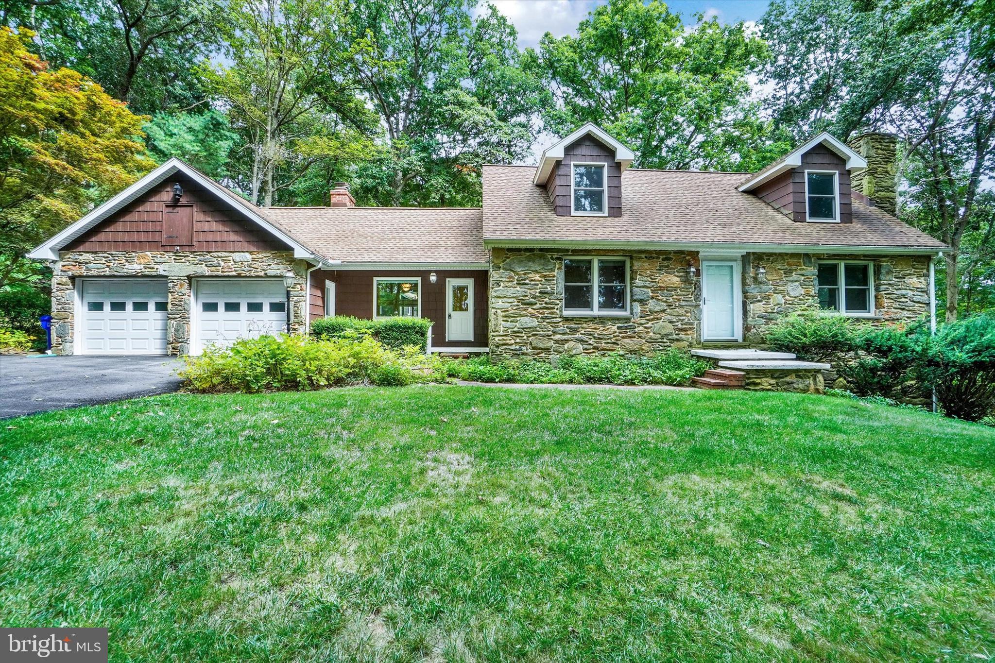 This fantastic, updated Cape Cod nestled in the middle of 11.73 wooded acres is a hidden retreat, with lots of extras & outbuildings for all your needs! The custom built home captivates inside & out, with real field stone, restored  brick & shake exterior, & beautifully renovated interior boasting hardwood floors on main level, formal living room, totally refinished Kitchen equipped with custom cabinets, recessed lighting, granite counters, large island/breakfast bar & superior SS appliances including gas cook top, built in double ovens & beverage fridge, adjacent den with built-ins & gas fireplace, & light-filled sun room with vaulted ceilings, exposed beams, skylight, walls of windows & French doors to the deck. The first floor primary suite offers updated bath with custom built tile shower & granite-topped double vanity.  Upstairs, 2 generous bedrooms are served by full bath with tub shower. Finished walk-out lower level has gorgeous field stone fireplace, huge family room, full bath & canning kitchen. Additional delights throughout the secluded grounds include abundant nature & wildlife,  attached 2-car garage, above ground pool with composite deck, 2 story bank barn with workshop in upper level & storage in lower level, plus additional 3 car shed. Tucked back the long, paved driveway, you'd never know you're just minutes to Stewartstown, New Freedom, MD Line & 83.  Privacy at its best!