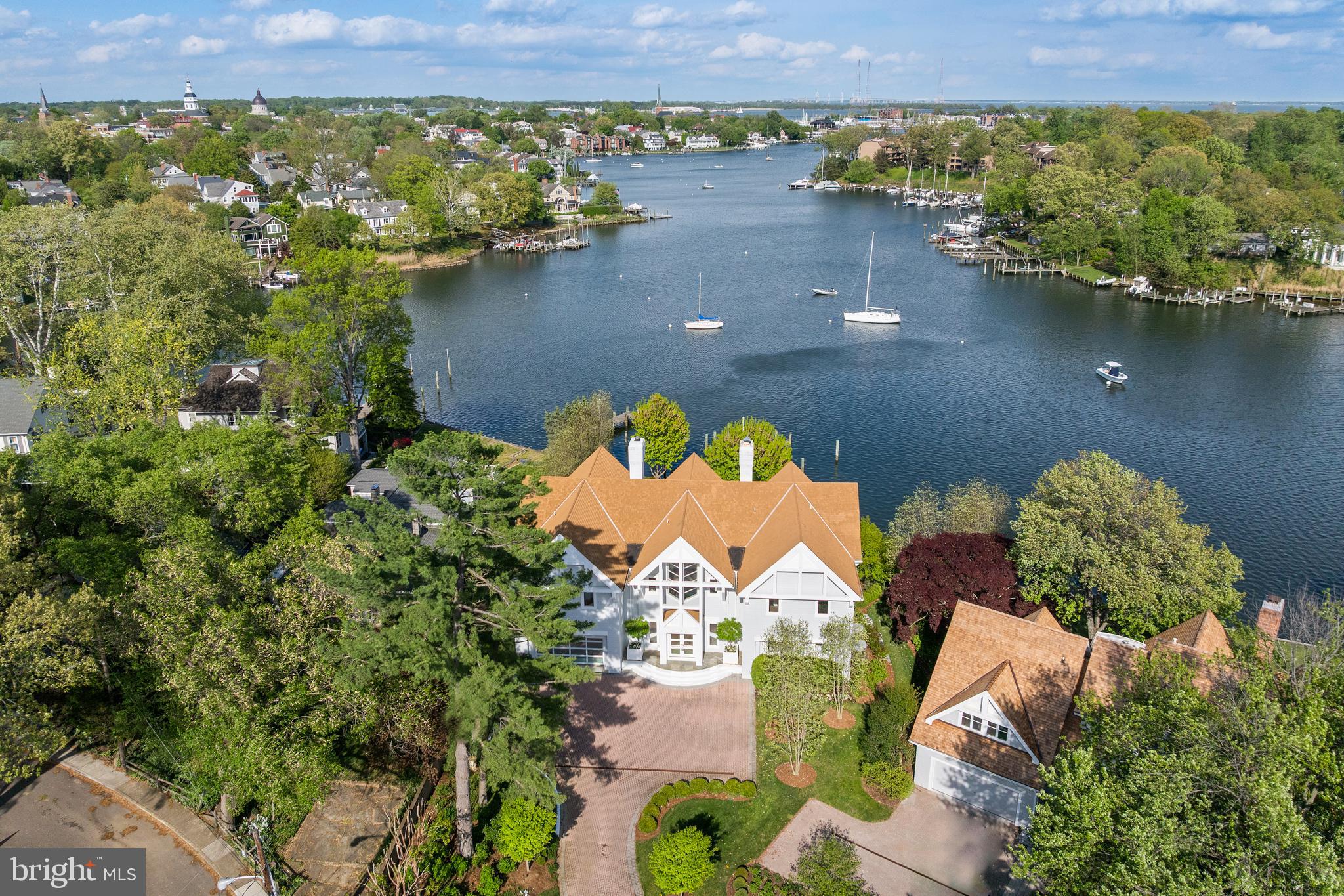 Experience one of the few Annapolis waterfront estates where you can leave your private dock and arrive at City Dock in minutes. Ideally situated on Spa Creek, this exceptional property captures the essence of Annapolis waterfront living with panoramic water views, unobstructed views of the Annapolis skyline, and endless opportunities for boating, kayaking, paddleboarding, and entertaining. Cruise by boat to downtown Annapolis, waterfront restaurants, ice cream shops, and the historic City Dock, or enjoy spectacular views of the Blue Angels, fireworks, and the annual boat parade from your own private retreat.
Set within an exclusive enclave of only three prominent waterfront residences, this property offers a rare combination of privacy, convenience, and lifestyle. The waterside heated saltwater pool, expansive Ipe deck, and beautifully landscaped grounds create the perfect setting for entertaining family and friends. Host sunset dinners, summer gatherings, or relaxed afternoons outdoors while enjoying the water views and the sparkling lights of the Annapolis skyline. Surrounded by lush boxwoods and specimen plantings, the grounds provide a peaceful escape just minutes from downtown.
Architecturally distinctive and thoughtfully updated, the residence combines refined design with comfortable waterfront living. Extensive renovations by Pyramid Builders showcase exceptional craftsmanship, including a dramatic marble foyer, floor-to-ceiling windows, solid wood doors, and rich stained black oak flooring. The gourmet kitchen features Sub-Zero refrigeration, a white six-burner Viking cooktop, high-gloss Premier cabinetry, Neolith porcelain countertops, designer lighting, and a striking floating staircase. A custom marble-topped bar provides an ideal space for entertaining.
Offering 4–5 bedrooms, 5 full baths, and 1 half bath, including a desirable first-floor bedroom suite, the home provides flexibility for family and guests. A two-car garage, generous parking, and deep-water pier complete this exceptional Annapolis waterfront offering.
This is more than a home—it is a rare opportunity to experience the very best of Annapolis living, where boating, entertaining, and downtown charm come together in one extraordinary setting.