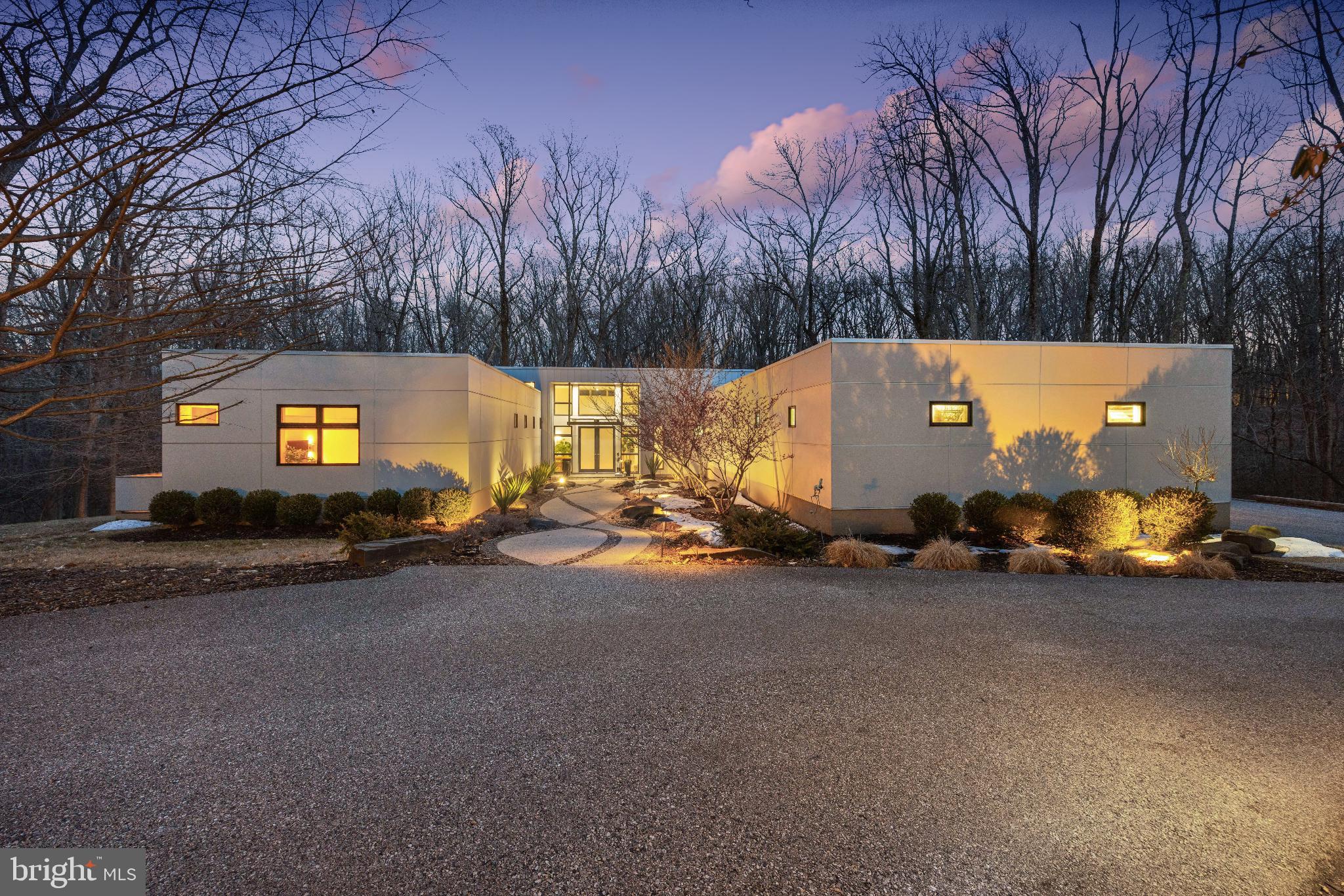 Welcome to this exquisite 2010 contemporary residence nestled on 2.5 private acres in the heart of Greenspring Valley. This stunning 4 bedroom,  5 and 1 half bath home designed by renowned architect, Chris Pfaeffle, offers peaceful tranquility with a focus on eco-friendly luxury. With 5219 square feet  of total living space, the home is bathed in natural light thanks to the abundance of oversized windows, creating walls of glass which brings the outdoors in offering magnificent views of nature. High-end finishes and upgraded lighting throughout the entire house create a modern, elegant ambience.  The interior features natural materials like beautiful Teragren bamboo floors, custom bamboo kitchen cabinets, Loewen double pane windows and 8’ solid wood doors, and thoughtfully upgraded lighting, all on dimmers, make it easy to create ambience in every room. Ceilings of 10’ to 16’ add to the feel of openness and the windows at the top let even more light in. The fireplace and cushioned window seat in the living room, create a warm feel, while the wall of built-in cabinets and bookshelves anchors the room. Be drawn to the incredible nature views outside thanks to the walls of glass and windows. The light-filled kitchen features a suite of 2023 GE Café appliances, including 2 dishwashers, a French-door oven, a built-in microwave and electric induction cooktop with a venting drown-draft. An abundance of cabinet space, instant hot-water and island with extra seating make this an efficient and inviting area.  The primary suite is a serene retreat featuring a built-in king bed, large custom closet area, long cushioned window seat and private Ipe deck, perfect for listening to the sounds of nature.  The en suite bathroom with recycle glass countertops and high-end finishes is a perfect blend of luxury and sustainability. Each additional bedroom is nicely appointed and offers large windows with views, all of the bedrooms have en suite bathrooms. The guest wing includes its own private Ipe deck. The bathrooms are meticulously designed with cherrywood accents and cabinetry, and state-of-the-art fixtures offering both functionality and elegance. Experience true indoor-outdoor living with a large Ipe and glass cantilever deck with seamless sight lines into the treetops and lush greenery. The outdoor kitchen features an imported Italian pizza oven and a new 2026 stainless steel gas grill, both plumbed for on-demand use, whenever the urge to grill and entertain strikes. Feel the allure of the saltwater HotSprings spa, which was added in 2021. Beautiful lighting, lines the exterior of the property, decks and driveway.  Additional living space in the lower level gives owners who need office or flexible space, several great options. A larger office space with custom built-in cabinetry, Brazilian stone countertops and an additional study, both with sliding glass doors to a patio could be easily reimagined for a new owner’s needs. Unwind and rejuvenate in the fully matted gym also with sliding glass doors to outside. A large cedar closet, a dog-washing station, and a 5th full bathroom, all complement the lower level well. The home includes a large 3-car garage, plus parking space for 6 additional cars. The entrance welcomes you with a new automatic driveway gate featuring beautiful ironwork. Just outside the garage is a ChargePoint universal EV charger for your electric vehicle, a whole-house generator for preparedness. Hardy panel on the exterior is an excellent choice for durability and style. Water comes from a private 400’ well and uses a salt-based conditioning and UV light water filtration system to ensure highest water quality. The house uses geothermal for heating and cooling, and also features radiant floor heating throughout for extra comfort and warmth. Conveniently located with quick access to 695 and 83, it's close to shopping, restaurants, county amenities. You too can make this your own personal paradise.