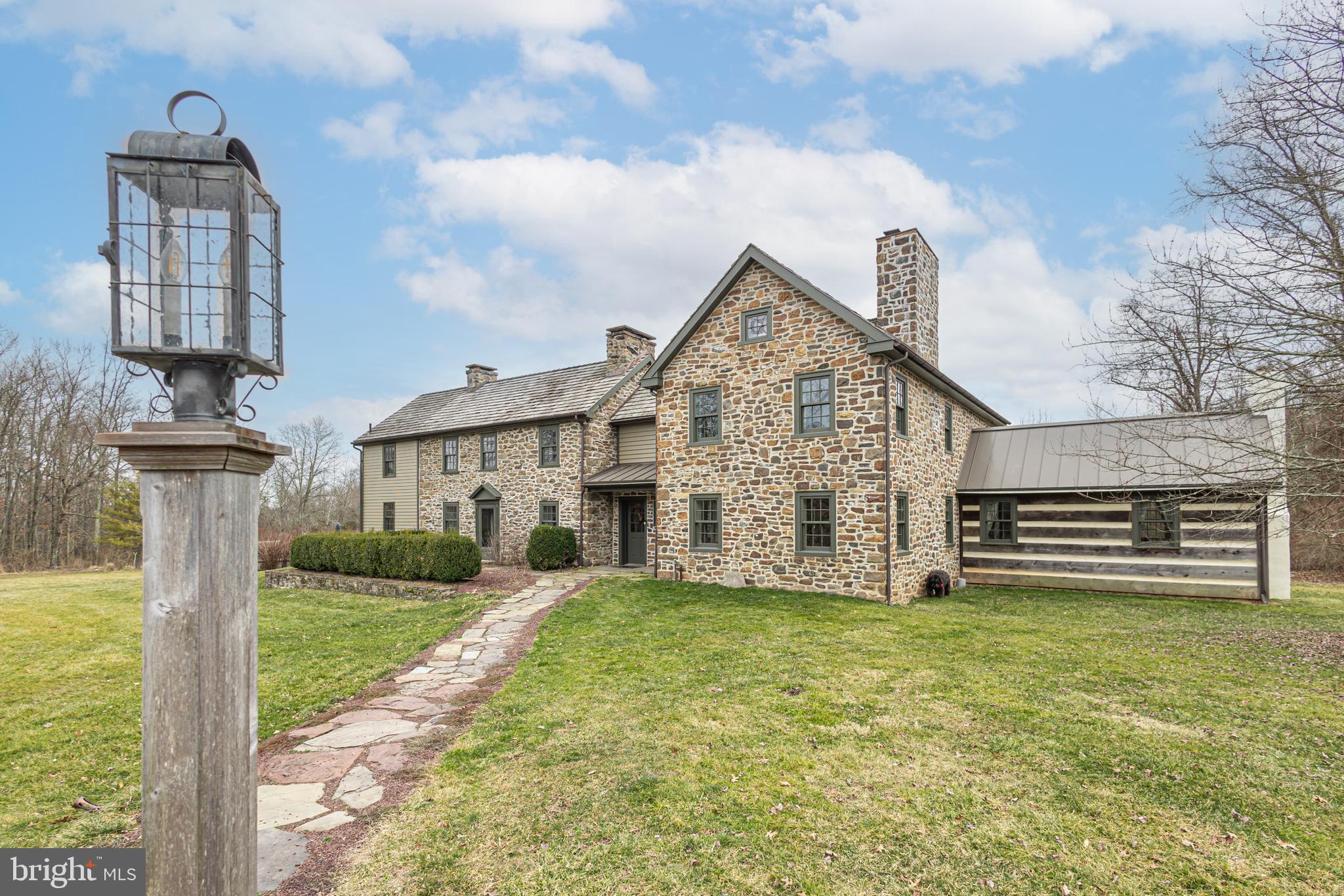 Discover this 18th-century Bucks County retreat set upon 10 private and tranquil acres of rolling lawns, native blooming meadows, lush woodlands, and stately stone walls. Originally built in 1737 and renovated and expanded in 2009 by the current owner, this lovely stone and frame farmhouse boasts every modern comfort while celebrating its colonial heritage. Upon entry, you’re welcomed by historic charm and details throughout with wide-plank pine floors, deep windowsills, and exposed stone. The sun-drenched dining room and living room feature a mantled fireplace and a wall of French doors leading to a stately stone patio. The cozy wainscoted family room is adorned with an exposed beamed ceiling and an original stone fireplace leading to an expansive chef’s kitchen. With abundant custom cabinetry, soapstone counters, a farm sink, a beautiful 6-burner gas range/oven, and a breakfast nook draped with dual patio French doors offers an exceptional backdrop for entertaining. The main level also includes a half-bath, convenient mud room with a hidden dog shower, and a private guest wing with a bedroom, full-bath, and a private entrance. Ascend to the second floor via the centrally located turned staircase to find a ship-lap accented primary suite complete with a wood-burning fireplace, 2 walk-in closets, and a full spa-like bath. Two additional bedrooms, with access to a full bath and a laundry room, overlook the picturesque grounds. Level three will surprise you with a wonderful flex space that could easily be used as a relaxing reading nook, office, or hobbyist's studio. Downstairs, the finished basement is currently being utilized as an office and fitness room. Outside, surrounded by the serenity of nature, is a secluded saltwater pool with hot tub and cabana, amazing stone patios with peaceful views, a useful chicken coop, and a collection of gardens that enhance the grounds. This breathtaking property also offers a renovated, multi-level barn complete with a kitchenette, full bath, laundry room, and plenty of versatile open space providing a comfortable haven for large family gatherings. The barn also offers exterior shed space and the nearby hanger supplies sufficient room for lawn and garden equipment. Additional amenities include a generator, radiant heat, UV light water filtration and so much more! Just 90 minutes from NYC and 45 minutes from Philadelphia this is a rare country oasis nestled between the Delaware River and Ralph Stover State Park and just minutes from the shopping and dining of New Hope, Frenchtown, and Doylestown.