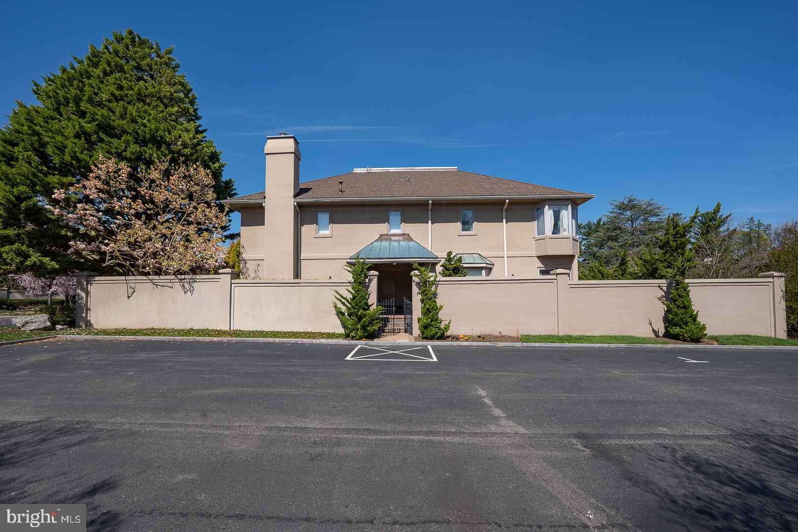 This elegant residence in Bala Cynwyd offers a refined, maintenance-free lifestyle with 24-hour security, elevator access to all levels, and a thoughtful balance of grand-scale living and everyday comfort. Sun-drenched interiors are highlighted by a dramatic formal living room with soaring ceilings, a gas fireplace, and expansive glass doors that invite abundant natural light while preserving privacy and a seamless indoor-outdoor connection.
Just off the entry, an inviting informal living room features rich wall paneling, custom built-in shelving, a wet bar, and a second gas fireplace—perfect for intimate gatherings or relaxed entertaining. A gracious dining room and a full bath on the main level add to the home’s functionality and flow.
The home offers three bedrooms and four-and-a-half baths, including an expansive primary suite designed as a private retreat with multiple closets and two full bathrooms, one featuring a large soaking tub. An additional bedroom with full bath is located on an upper level, along with a conveniently placed laundry room.
The finished basement provides exceptional flexibility and includes a private bedroom with a full bathroom, ideal for guests, office space, or extended living. Additional highlights include a two-car garage, driveway parking, and comprehensive exterior services—lawn care, snow removal, trash service, and exterior maintenance—allowing for truly effortless living in a quiet, private setting.