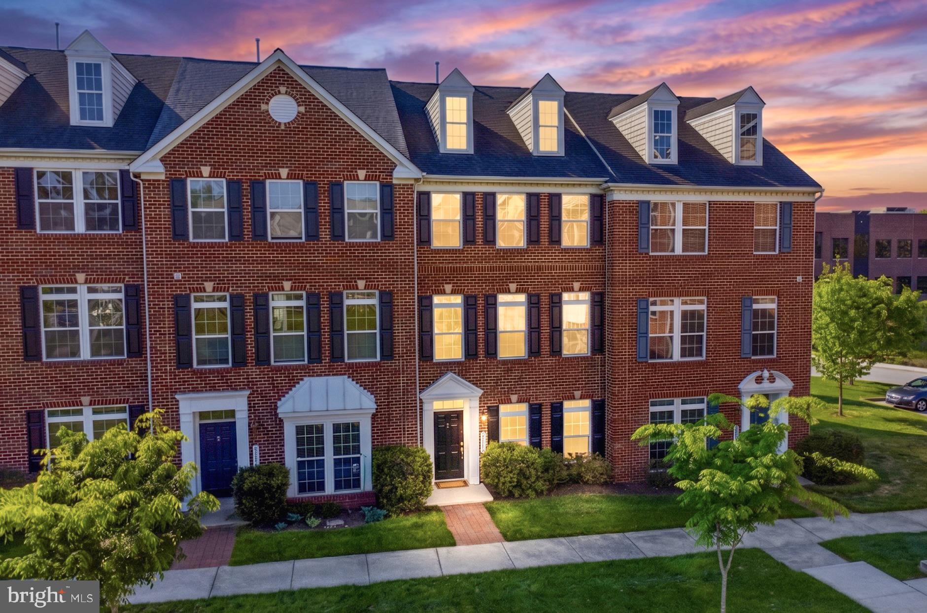 Welcome to this beautifully maintained, expansive brick-front townhome, where abundant natural light and an elegant design create an inviting atmosphere from the moment you arrive. A truly rare find in townhome living, this property boasts effortless parking and storage with a two-car garage and an accompanying two-car driveway. The versatile entry level is thoughtfully designed to adapt to your lifestyle. It features a bright, flexible space perfect for a fourth bedroom, private home office, or media room, alongside an additional spacious room already roughed-in for a third full bathroom. A dedicated laundry and mudroom area with a convenient closet completes this highly functional ground floor, keeping everyday clutter out of sight. Upstairs, the main level showcases a breathtaking open-concept layout grounded by gleaming hardwood floors and illuminated by large transom windows. At the heart of the home is a gourmet kitchen outfitted with 42-inch cherry cabinetry, sleek granite countertops, a massive walk-in pantry, and updated stainless steel appliances (2021). This culinary space flows seamlessly into a sprawling family room and out to a beautiful composite deck, offering an ideal, low-maintenance setting for morning coffee or evening entertaining. A well-placed powder room perfectly serves this central gathering space. The hardwood flooring continues onto the upper level, which hosts three generously sized bedrooms and two full bathrooms. The true showstopper is the luxurious primary suite. This private sanctuary boasts a large walk-in closet and a spa-inspired en-suite bathroom complete with a dual-sink vanity, a deep soaking tub, and a custom-tiled shower. Elevating the suite further is a stunning private loft, featuring a beautifully designed wet bar and wine refrigerator, the ultimate retreat for a secluded home office, elegant sitting room, or cozy reading nook. Perfectly situated for ultimate convenience, this home offers unbeatable accessibility to the premier shopping and dining at Arundel Mills Mall, as well as major commuter hubs including the NSA, Fort Meade, and BWI Airport. Seamlessly blending executive comfort, sophisticated style, and an unmatched location, this move-in-ready gem is an exceptional opportunity you will not want to miss.
