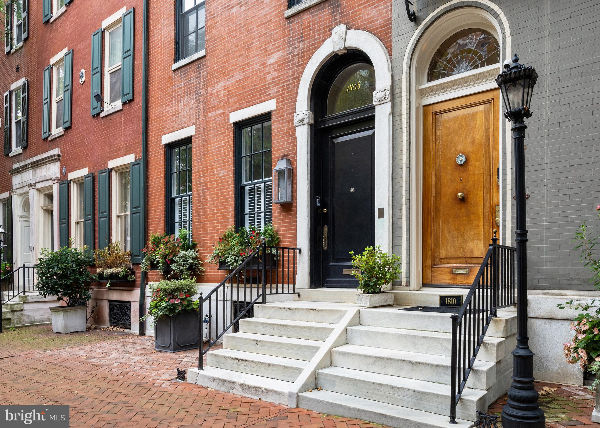Welcome to 1808 Delancey Street—a masterfully restored residence on Philadelphia’s most coveted block. Originally built in 1870, this home underwent a mid-century renovation in 1952 that stripped it of its historic charm. However, an 18-month restoration in 2017 revived its timeless elegance, seamlessly integrating modern luxury with historic detail.

The first floor opens to a lovely foyer that leads into a sophisticated living room. Custom designed with three elegant arched openings, the space is anchored by a ventless gas-burning fireplace with an Italian mantel, surrounded by graceful chandeliers. A newly added powder room provides convenience while maintaining the home’s refined aesthetic.
A few steps up, the dining room offers custom cabinetry, a wine fridge, and access to a private deck with an irrigation system—perfect for al fresco entertaining. Adjacent is a designer kitchen by J. Thom and Joanne Hudson, featuring custom cabinetry, granite countertops, a tile backsplash, and high-end appliances. An arched pass-through between the kitchen and dining room enhances both function and charm.
The second floor is thoughtfully divided into two distinct spaces. At the rear, a luxurious family room is equipped with a nine-speaker Dolby Atmos surround sound system and motorized shades, creating a premier entertainment area. This level also has an additional powder room.

At the front, the primary suite has been completely reimagined for elegance and functionality. The bedroom boasts a gas fireplace, a tray ceiling with dimmable perimeter lighting, and a walk-in closet with custom interiors. The spa-like en suite bathroom features custom cabinetry, a large tiled shower, and a Biobidet, elevating everyday comfort.

The third floor includes two additional bedrooms, each with its own en suite bathroom. One bedroom is currently used as an in-home office, and this floor also features a well-equipped laundry room with custom cabinetry and a wash sink.

The fourth floor is a self-contained guest suite, complete with a bedroom, bathroom, and kitchenette. From this level, ascend to the stunning rooftop deck, which features a gazebo, an irrigation system, and panoramic views of Philadelphia’s skyline.

The garage has been expanded from a single-car space to accommodate three vehicles, complete with a Tesla charging station—offering a rare blend of practicality and luxury.
Throughout the home, meticulous upgrades abound. These include a four-stop elevator, historically accurate windows, new flooring, and updated electrical and plumbing systems. A multi-zone heating and cooling system, Lutron lighting, instant gas water heaters, WiFi transmitters, and in-ceiling Sonos-integrated speakers add to the home’s modern conveniences.

1808 Delancey Street is more than a residence; it’s a masterpiece of design and functionality, offering historic grandeur and cutting-edge amenities in Philadelphia’s premier location. This extraordinary property is truly a one-of-a-kind legacy home.