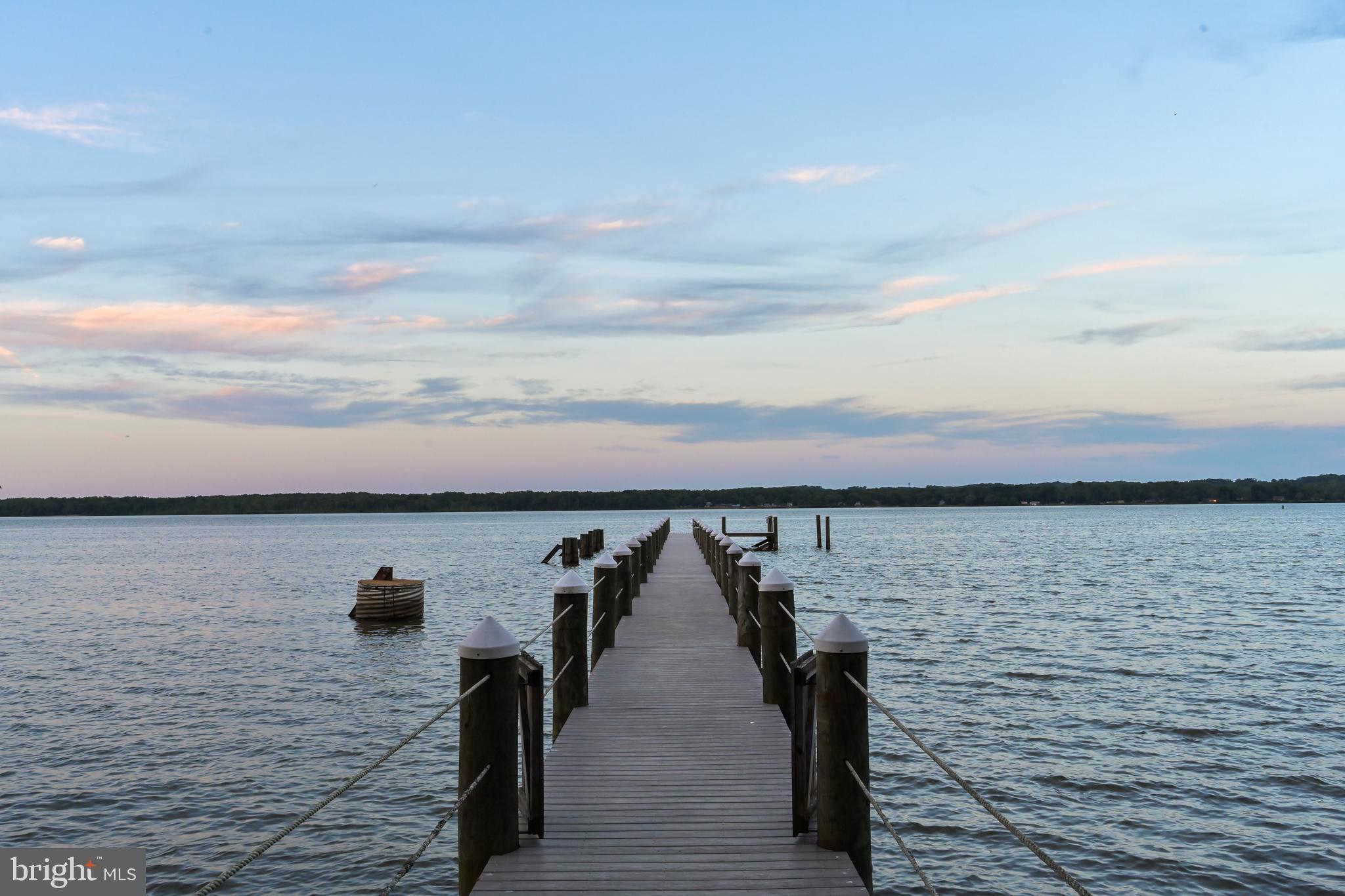 A Waterfront Masterpiece on The Potomac River, just 35 minutes from Washington, D.C., awaits in the enclave of Mason Neck—a sanctuary in Northern Virginia. Known for its expansive regional & state parks, pristine nature & wildlife reserves, equestrian facilities, and golf course, this area offers an unparalleled lifestyle of sophistication and serenity. Historically significant, the land was once the home of George Mason, a Founding Father and author of the Virginia Declaration of Rights, adding a rich cultural heritage to its allure. This distinguished estate boasts over 225 feet of breathtaking waterfrontage where you can drive down to a 269-foot private dock (no stairs), epitomizing an exclusive water-centric lifestyle. As you traverse the gated circular entry and immaculate grounds with beautiful native & ornamental plantings, you are greeted by the stately front motor court. Designed by the visionary architect Tom Flach and constructed by the renowned KohlMark Group, this craftsman-style residence showcases exquisite bespoke finishes throughout. Enter through an artisan-carved stained glass door into the grand foyer, where a majestic barrel vault ceiling with cedar wood inlay and elegant cove lighting adorns the travertine center hall. Panoramic water views grace every space on the main level. The formal living room features a coffered ceiling, an opulent marble-surround wood-burning fireplace, and custom built-ins. The adjacent formal dining room, also with a coffered ceiling and intricate crown moldings, opens to luxurious outdoor entertaining spaces with breathtaking river views. The gourmet kitchen, clad with richly painted cherry cabinetry, lustrous quartzite countertops, and an expansive island, boasts professional-grade stainless steel appliances. A rear pantry with commercial-grade appliances, a main level laundry, and rear staircase complement the kitchen. The breakfast area opens to the hearth/ family room, featuring a striking cedar cathedral ceiling, a grand stone fireplace, custom built-ins, and sweeping water views. In the left wing, an octagonal library opens to the rear patio. An elegant office or optional bedroom with a full bath and walk-in closet, along with a refined study featuring a wet bar, opens to a private screened-in porch. Ascend the staircase, adorned with a stunning blue heron stained glass window, or take the private elevator to the upper level. Double solid wood doors open to the sophisticated primary suite sitting room with a marble gas fireplace and captivating water views. The primary bedroom features another stunning cedar cathedral ceiling and a bowed bay window. The spa primary bath, with split vanities, luxurious marble finishes, and an oversized shower, has a second entry from the wardrobe hall lined with built-ins leading to two expansive walk-in closets. The upper front hall, with custom built-in benches, leads to secondary bedrooms, each with en-suite baths showcasing designer finishes. Beyond the upper-level laundry room and powder room lies an engaging game room or optional fifth bedroom. On upper level 2, a fully unfinished space offers boundless potential for future expansion. The lower level features an expansive exercise room, full bath, and a walk-out level recreation room. With over 2,300 square feet of unfinished space, there is ample opportunity for additional customization. The meticulously landscaped rear grounds include a grand stone patio, ambient landscape lighting, an inviting fire pit, and commanding views of the majestic Potomac River. The community features a waterfront park with a beach, pavilion, boat launch, tennis, volleyball, and basketball. This exquisite location is near Old Town Alexandria, Fort Belvoir, & VRE Station, and has easy access to I-95 enhancing this retreat's appeal. This haven is a paradise for nature enthusiasts & boating aficionados alike, embodying unparalleled sophistication, elegance, & refined living—a true waterfront masterpiece.