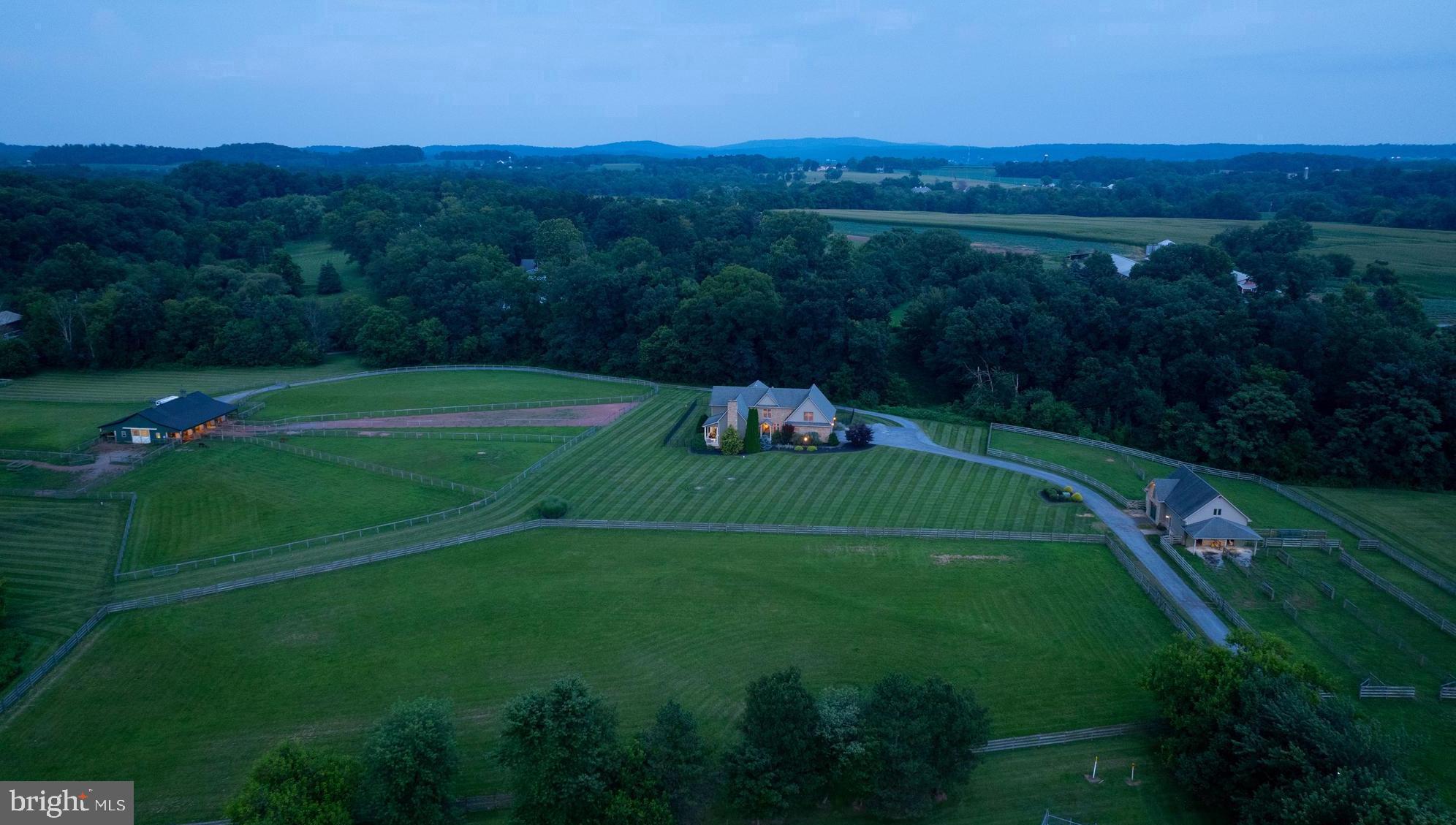 Welcome to 380 Meadow Lane, a stunning 31.47± acre estate nestled in the peaceful countryside between Elizabethtown and Hershey, PA. This desirable property offers a tranquil blend of fenced pastures, wooded areas, open field, and lawn, all surrounding a thoughtfully designed custom home w/open floor plan, a large center isle barn, a charming carriage barn, and run in shed. A long, tree-lined driveway provides a graceful approach to the private setting, revealing breathtaking views of the rolling countryside. The covered front door invites you into a welcoming two-story open foyer w/beautiful staircase. Just off the foyer, you enter a spacious open living area comprising the great room, kitchen, and dining space - all featuring wide plank wood floors, creating a memorable space for entertaining.  The great room serves as the centerpiece of the home, showcasing a soaring cathedral ceiling w/exposed beams, an impressive floor-to-ceiling stone propane fireplace with a wood mantel flanked by built-ins on both sides, and a door opens to a covered porch where you can relax while enjoying the views and watching for deer & abundant wildlife.  The large kitchen features a breakfast bar w/wood counter, pendant lighting, and seating for six, an island with butcher block counter, recessed lighting, multiple wall cabinets w/glass doors, desk space, large pull-out drawers, tile counter & backsplash, wine rack, and a farmhouse sink overlooking the family room. Stainless steel appliances include a GE Monogram refrigerator, a 6-burner propane range w/electric oven, and Thermador range hood.  The adjacent dining area is lined with windows, providing majestic views & plenty of space for large gatherings.  The family room features a stone floor and abundant natural light, creating a cozy spot to unwind. A powder room with a pedestal sink is thoughtfully located on the first flr. The mudroom/laundry area offers access to both the garage and fenced backyard and includes tile flooring, a pet bath, washer & dryer, laundry sink, and built-ins with a counter and bench seat.  Both the first floor and primary bath have comfortable radiant floor heating.  The rear patio provides an ideal space for outdoor entertaining.  The spacious primary suite boasts a vaulted ceiling, propane fireplace, sitting area, large arched window overlooking the pastures, a large walk-in closet with built-ins, and a primary bath with heated tile floor, tile shower, double sink vanity, and whirlpool tub. Just outside the primary suite is an office loft overlooking the great room and plus an additional loft area w/built-ins.  Two additional large bedrooms offer plentiful closet space. The oversized two-car garage features large carriage house-style doors approximately 9’11” wide by 7’11” high. The carriage barn includes an overhead door to a garage space, a stable, overhangs on both sides, and a hayloft. The large center isle barn measures 36’ W x 60’ L, w/overhangs on both sides, featuring a heated & cooled tack room w/bathroom, two horse stalls, and space for five additional stalls if portable fencing is used. The property is enrolled in Act 319 Clean & Green. This location offers a rural setting while being centrally located to Lancaster, Hershey, & Harrisburg, and is approx. five minutes from the Rt. 283 Elizabethtown/Hershey exit. It’s about 20 minutes to Harrisburg International Airport, 1¾ hours to Philadelphia International Airport, and 2 hours to Baltimore International Airport.  This may be a once-in-a-lifetime opportunity to acquire this rare property!  Note: Many mapping programs are not reflecting the property lines correctly – see lot plan w/listing documents for property lines.