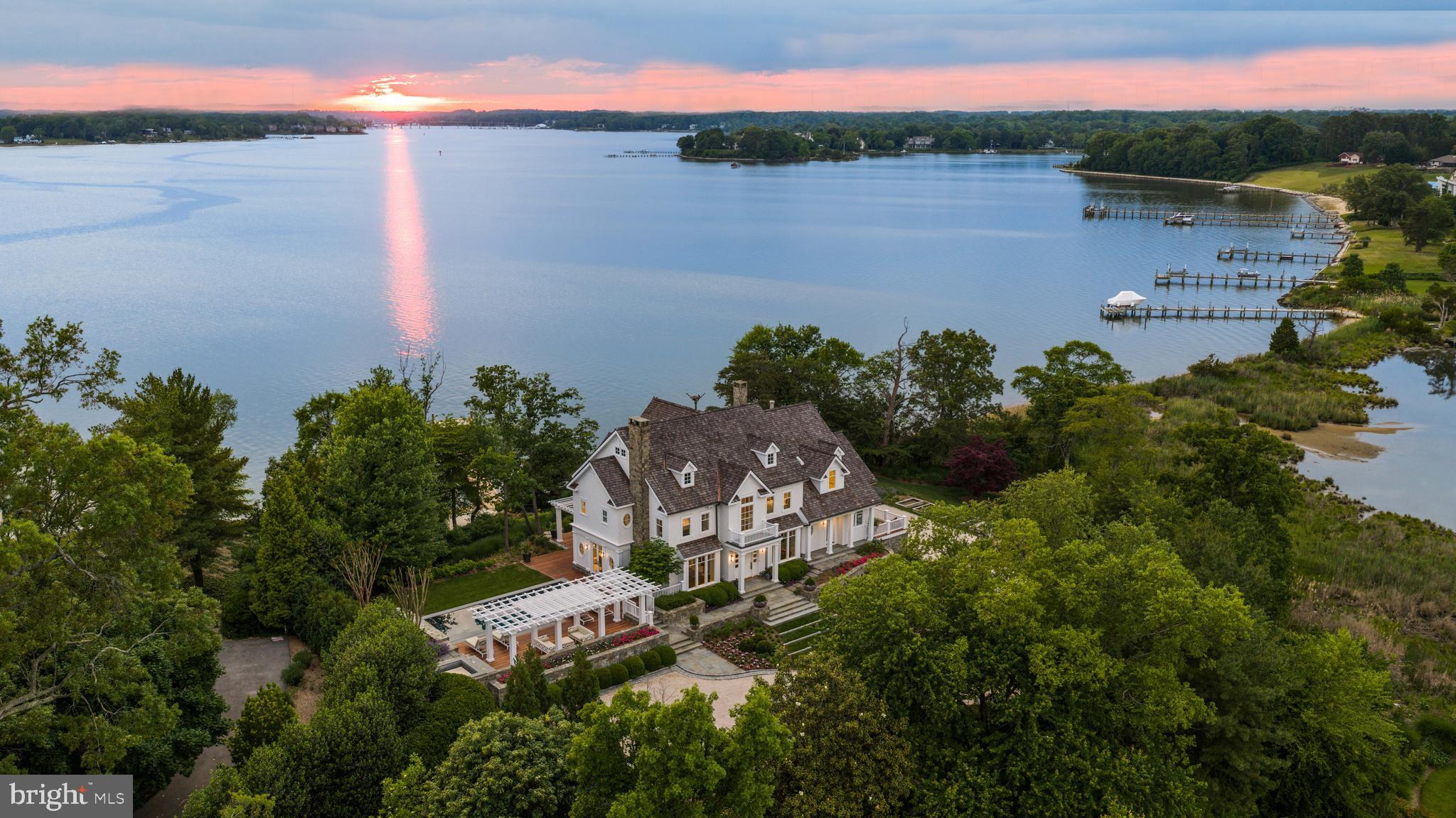 An extraordinary expression of waterfront luxury, this architecturally significant estate represents a rare convergence of world class design, craftsmanship, and lifestyle. Located within the prestigious enclave of Wimbledon Farms, surrounded by grand estates and moments from local vineyards and equestrian facilities, the residence was masterfully conceived by acclaimed architect Scarlett Breeding and flawlessly built by Pyramid Builders. A complete refit elevated the home to an uncompromising standard where timeless architecture and modern sophistication exist in perfect harmony.

An enchanting winding crushed gravel driveway framed by Belgian block curbing sets the tone for the remarkable experience that awaits. Perfectly positioned with western exposure, the property captures breathtaking sunsets as golden light melts into the horizon across the river and the surrounding landscape. Professionally designed landscaping creates a lush resort like setting that enhances the home’s striking architectural presence.

Inside, high lacquered woodwork, bespoke millwork, hidden passage doors, attention to detail, and coffered ceilings create an atmosphere of refined sophistication. Ultra luxe Chesneys fireplace surrounds anchor multiple living spaces with warmth and elegance, while expansive walls of glass frame sweeping water views and seamlessly connect the indoors with the surrounding waterfront setting. A richly appointed wood-clad office with custom built ins offers an executive retreat designed for both privacy and inspiration.

At the heart of the residence, the extraordinary St. Charles kitchen rivals those found in internationally celebrated estates, featuring Premier custom cabinetry, a statement Le Cornue range and island, exquisite fixtures, and an artisan-crafted focal point range hood, all designed for elevated entertaining and effortless daily living.

Outdoor living reaches resort caliber with an elevated spa and a spectacular four sided overflow  vanishing edge pool, where the waterline sits flush with the pool edge, creating a seamless visual connection to the river beyond. Exotic Ipe hardwood decking surrounds the pool and expansive rear terrace, while pergolas and a screened porch provide beautifully designed spaces for entertaining and relaxation. A new private pier, private beach, and panoramic river and pond views complete this extraordinary waterfront lifestyle.

The upper level offers four luxurious ensuite bedrooms, including a phenomenal primary suite with sweeping water views, barrel ceiling, a fireside sitting room, a boutique inspired dressing gallery, and a spa quality bath with a soaking tub overlooking the water. Integrated Control4 home automation delivers effortless comfort and convenience throughout.

Tucked away on the coveted Annapolis Neck peninsula, Wimbledon Farms offers a rare blend of tranquility, exclusivity, and convenience. Just moments from Downtown Annapolis and major commuter routes, the setting feels worlds away, defined by peaceful surroundings and an unmistakable sense of retreat. Encompassing only 19 estate homesites, this intimate waterfront enclave is gracefully bordered by Harness Creek and the South River, creating a breathtaking backdrop for both sunrise and sunset vistas. Residents enjoy a warm yet private community atmosphere, highlighted by occasional neighborhood gatherings and an expansive marina on protected Harness Creek, a prized deep water haven known for its calm, sheltered waters and exceptional boating access. Welcome Home!