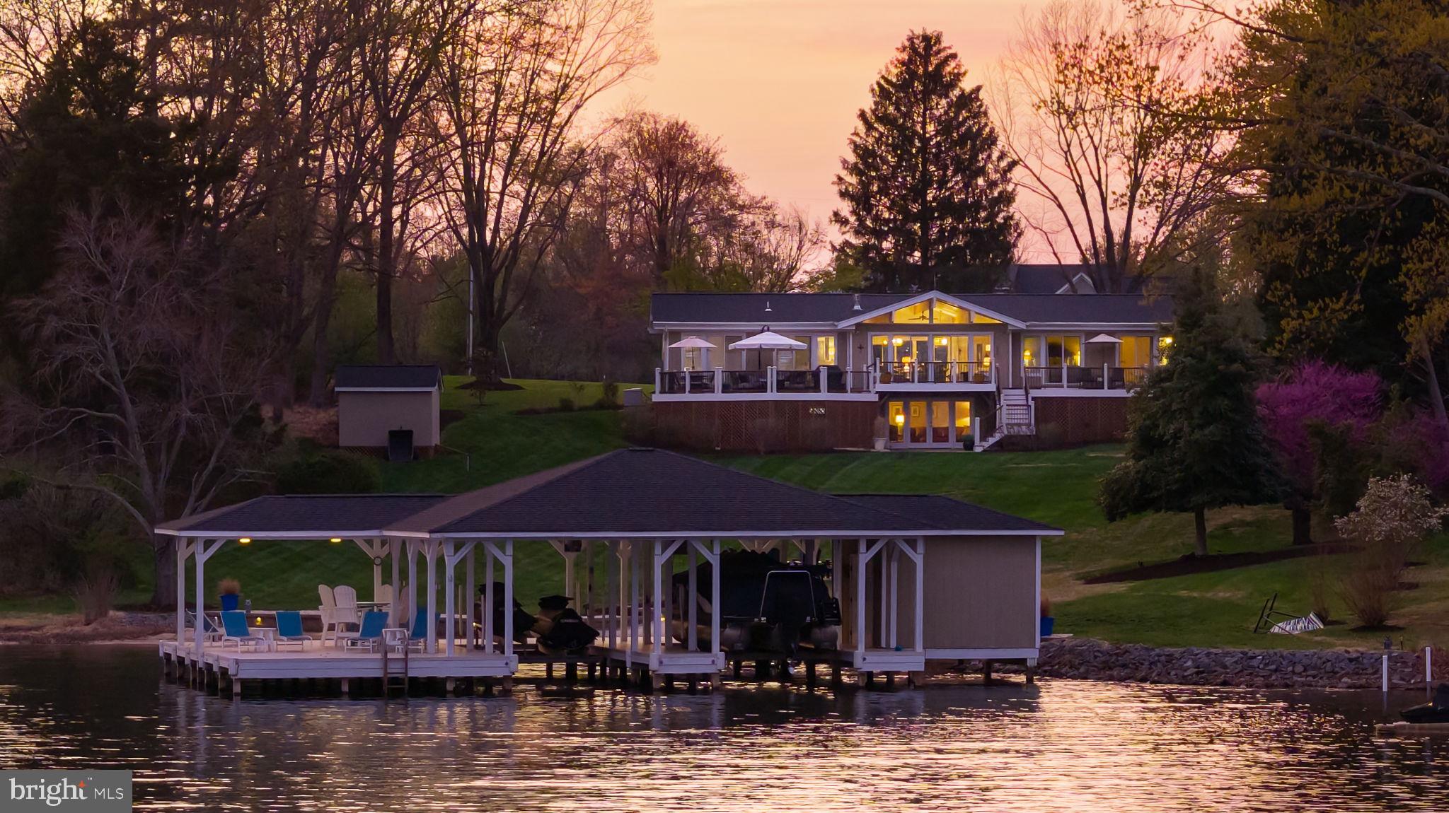 Experience iconic lakefront living in this stunning Lindal Cedar post and beam home, perfectly positioned on the public side of Lake Anna with breathtaking, unobstructed views across the widest stretches of the lake. 140 feet of stone and riprap shoreline, a sandy beach and deep clean water (10 feet at the end of dock), this property offers the ultimate waterfront setting. The impressive double-slip boathouse is designed for both convenience and enjoyment, featuring electric lifts with upgraded motors for both boat and jet ski lifts, WiFi, a spacious partially covered sun deck, and a storage room—everything you need for effortless days on the water. Inside, the home showcases timeless Lindal craftsmanship with vaulted ceilings, exposed beams, a gas stove, and rich maple hardwood flooring. The open-concept layout is filled with natural light and showcases stunning lake views from nearly every room. Offering 3,400 square feet (2,857 finished), this 4-bedroom, 3-bath home is thoughtfully designed for both relaxed everyday living and seamless entertaining. The main-level lakeside primary suite offers private deck access and a beautifully updated ensuite bath with a tiled shower. Two additional lakeside bedrooms also feature direct deck access and share a fully renovated bath. The updated kitchen is equipped with granite countertops, a breakfast bar, stainless steel appliances, and updated lighting in both the kitchen and dining areas. The walkout lower level expands your living space with a spacious family room, fourth bedroom, full bath, and a large storage/workshop area with the potential to be finished for additional living space. Outdoor living is just as impressive, with a newly installed stone seawall and beach area, riprap reinforcement, ambient shoreline and fire pit lighting, and a custom stone fire pit with a Breeo smokeless insert—perfect for unforgettable evenings by the water. Ideally located by both boat and car, you’re just minutes from marinas, local dining, and everyday conveniences. Extensively upgraded and thoughtfully maintained, this home is ready for new beginnings with you! Recent upgrades include new roofs on the house, boathouse, and shed (2021), a whole-house generator (2021), and a new hot water heater (2025). See full list of improvements and items that convey in MLS documents section. HOA is optional to join.
