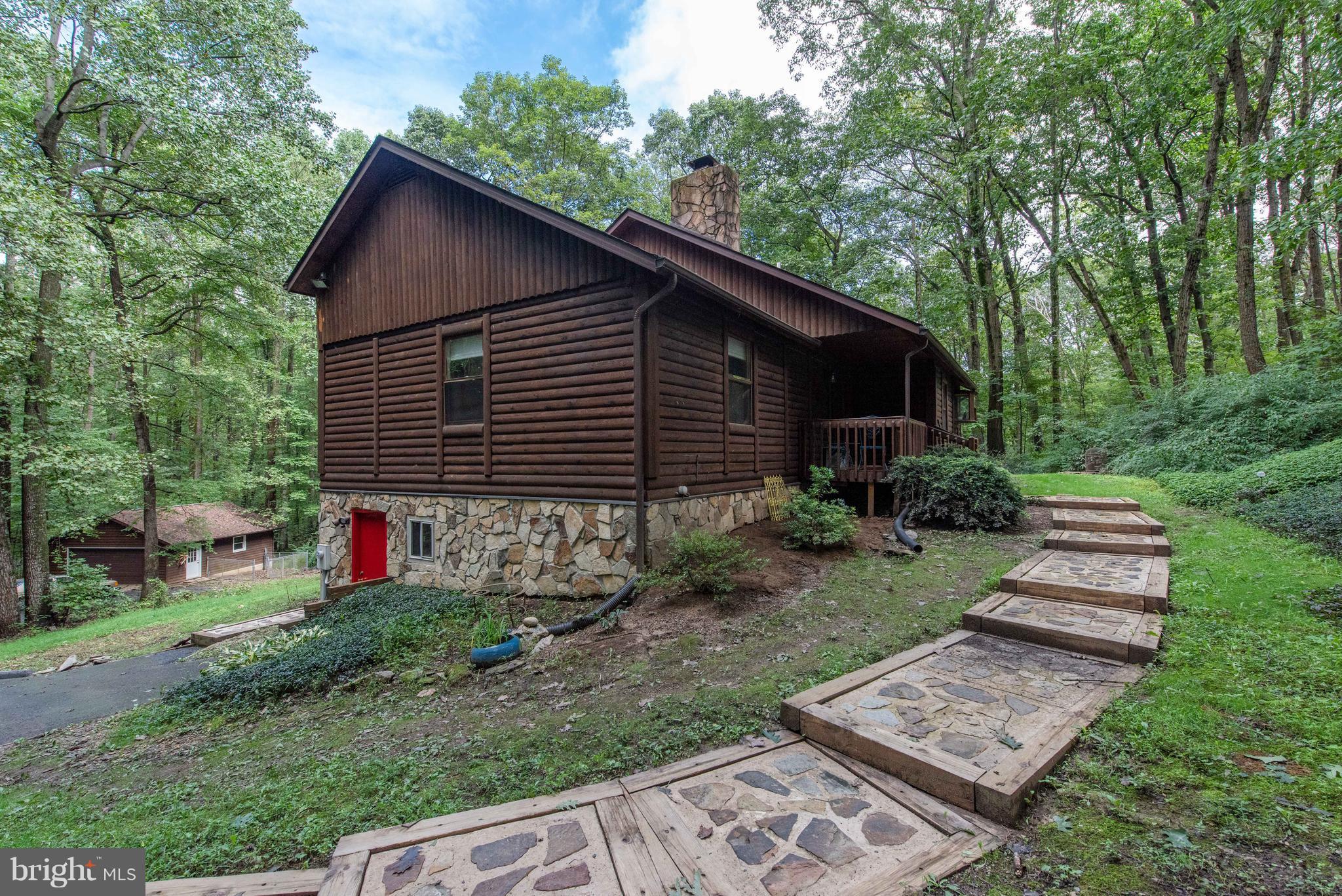 SELLER DROPPED PRICE! An  adorable log cabin on 4.47 wooded acres with a stream! 1378 SF, 3 bedrooms, 2 full bathrooms, cozy living room, and breakfast nook ,large screened in deck , and a large unfinished basement with a 2 car detached garage. Floor to ceiling stone fireplace with newer wood burning insert is the centerpiece of this family home. A one year home warranty and all appliances are included.  Location of this property makes it eligible for a no money down USDA loan. Commuting distance to Baltimore. Why wait to live out your Dreams?