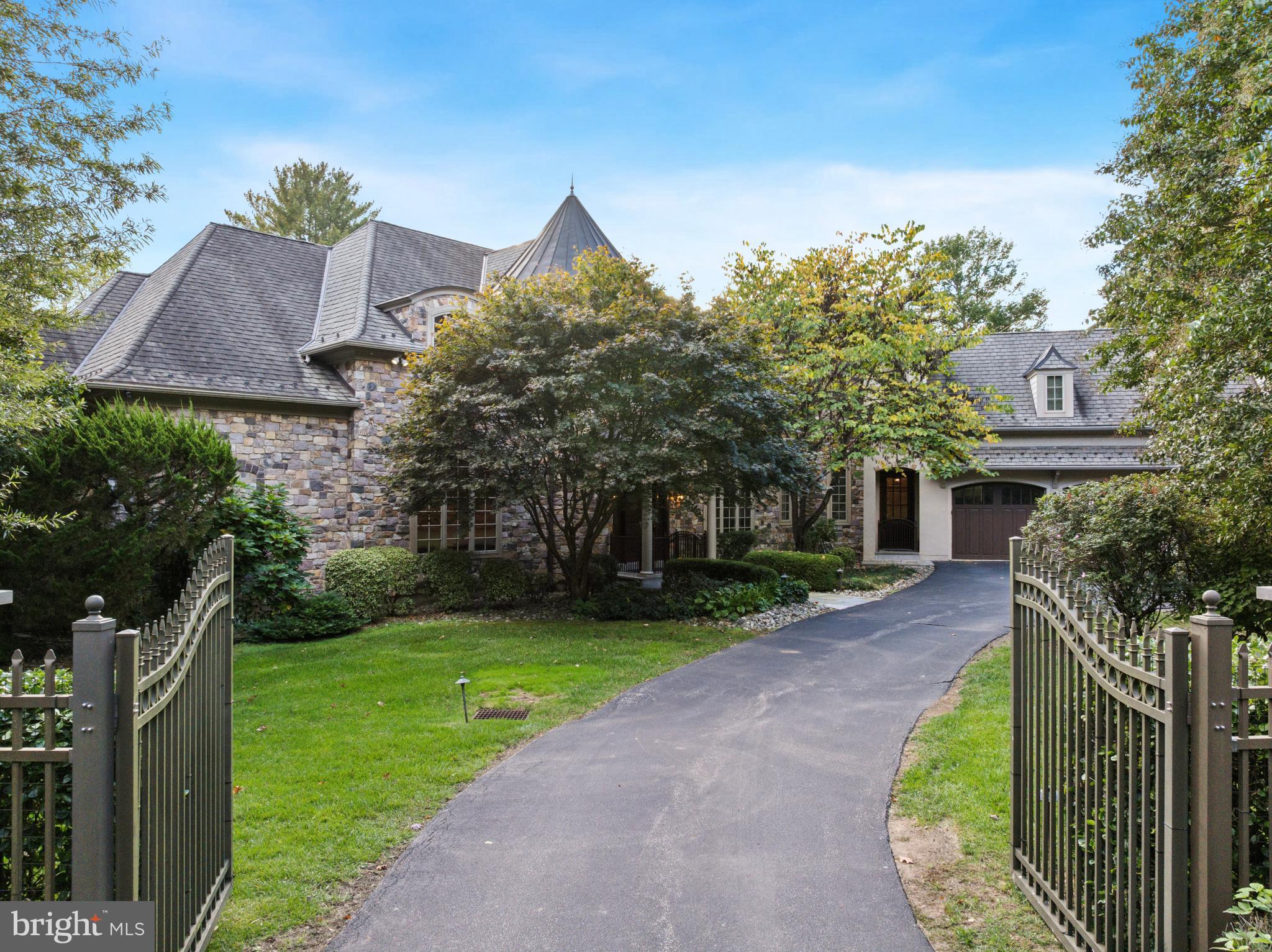 Elegant gated estate in sought-after Gladwyne, masterfully designed by renowned architects Peter Batchler alongside architectural designer, Christina Waters, offering exceptional craftsmanship, scale, and versatility. A grand two-story marble foyer with a sweeping curved staircase makes a striking first impression and opens to the spectacular great room, highlighted by soaring ceilings, a Heat & Glo gas fireplace, and custom built-ins with a lighted display and media center. This impressive space flows seamlessly into the chef’s kitchen, featuring rich custom cabinetry, an oversized center island with seating, and top-of-the-line stainless steel appliances, including a Thermador cooktop, a new refrigerator, double dishwashers, wall ovens, and a Sub-Zero wine and beverage refrigerator. A sun-drenched breakfast area with built-in bench seating overlooks the serene, private grounds. The stunning sunroom serves as a true indoor-outdoor retreat, complete with multiple seating areas, a dining space, hurricane-rated windows, and a full indoor grilling kitchen perfect for year-round entertaining, all with picturesque views of the lush backyard. The formal dining room, adorned with elegant crown molding, is ideal for hosting and is complemented by a well-appointed butler’s pantry. Additional main level highlights include a richly detailed home office with custom built-ins, two powder rooms, multiple pantry closets, and a spacious, well-equipped laundry room. The luxurious first-floor primary suite offers a private sanctuary, complete with a Heat & Glo gas fireplace, custom built-ins, and an expansive, professionally outfitted walk-in closet. The spa-inspired primary bath features dual vanities, separate water closets, a soaking tub, and an oversized glass-enclosed shower. The second level offers two generously sized bedroom suites with ensuite baths, along with two additional bedrooms connected by a Jack-and-Jill bathroom. A standout feature is the fully self-contained one-bedroom apartment with both private exterior access and interior connectivity, ideal for an au pair, in-law suite, or extended guests, complete with a living area, full kitchen, separate bedroom, full bath, and its own laundry. The finished walkout lower level provides exceptional additional living space, including a large media and recreation room, fitness area, full bathroom, a private office with exterior access, and abundant storage. Additional features include an elevator servicing all levels, a full-house generator and an oversized four-car garage, three HVAC systems with six zones, and beautifully manicured, private grounds. Ideally located just minutes from the Village of Gladwyne with convenient access to Center City Philadelphia, major roadways, premier shopping and dining, and situated within the highly acclaimed Lower Merion School District, this extraordinary estate offers refined Main Line living at its finest.