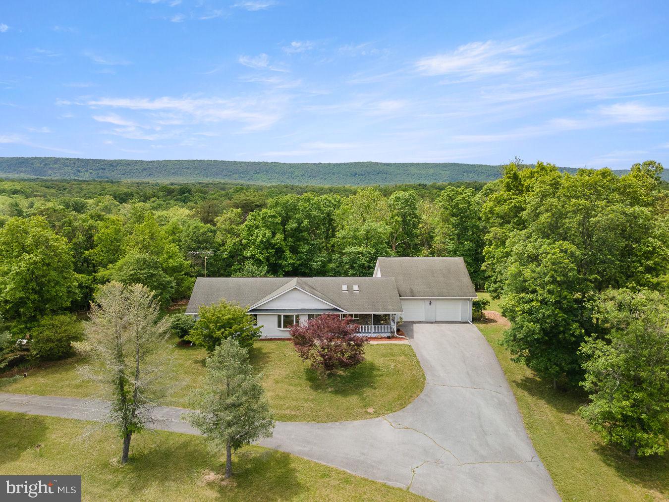 Dreaming of gorgeous views and your own peaceful retreat? This secluded and charming ranch home is situated on 10.7 beautiful unrestricted acres. Partially fenced with pastures and rolling countryside it's full of potential, this property is ideal for those seeking privacy, recreation, hobby farming, or simply room to roam. The main level offers convenient single-level living with 3 bedrooms, 2 full baths, and 1 half bath, separate laundry room, formal dining room, sunken living room open to kitchen is perfect for gatherings and entertaining. New stainless dishwasher, refrigerator, and stove complete the eat-in-kitchen. Thoughtful finishes throughout, including wood flooring, ceramic tile, and an abundance of storage closets. An oversized  32'x32' three-car garage provides ample room for vehicles, equipment, or workshop space. The fully finished lower level greatly expands the living space, featuring a second kitchen, a full bath, a large family room, a dedicated 16' x 24' workspace or hobby room with plentiful shelving, two bonus rooms, large walk-in closet and three large additional storage areas. Property has endless possibilities, this exceptional home offers space, versatility, and breathtaking surroundings. Sleepy Creek Management Area just minutes away!