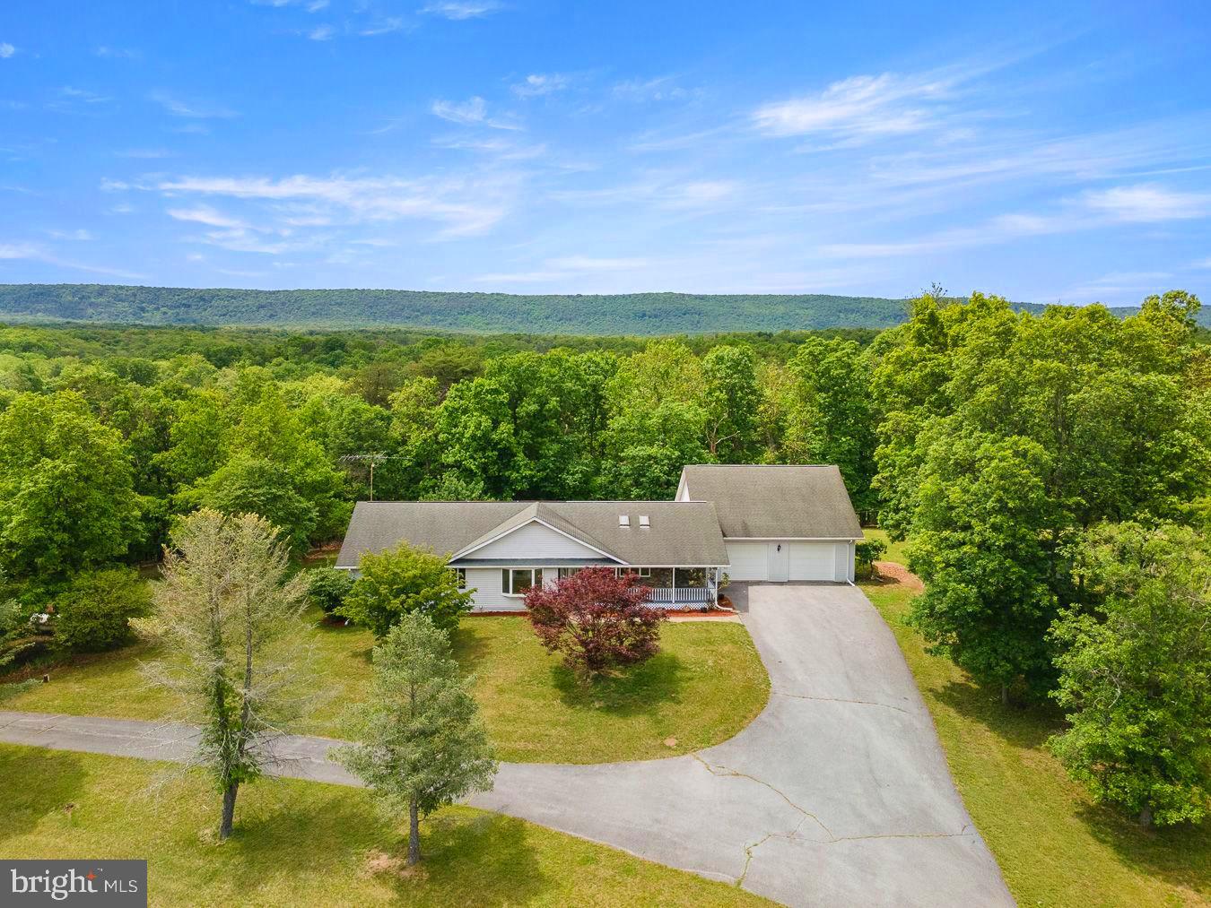 Dreaming of gorgeous views and your own peaceful retreat? This secluded and charming ranch home is situated on 10.7 beautiful unrestricted acres. Partially fenced with pastures and rolling countryside it's full of potential, this property is ideal for those seeking privacy, recreation, hobby farming, or simply room to roam. The main level offers convenient single-level living with 3 bedrooms, 2 full baths, and 1 half bath, separate laundry room, formal dining room, sunken living room open to kitchen is perfect for gatherings and entertaining. New stainless dishwasher, refrigerator, and stove complete the eat-in-kitchen. Thoughtful finishes throughout, including wood flooring, ceramic tile, and an abundance of storage closets. An oversized  32'x32' three-car garage provides ample room for vehicles, equipment, or workshop space. The fully finished lower level greatly expands the living space, featuring a second kitchen, a full bath, a large family room, a dedicated 16' x 24' workspace or hobby room with plentiful shelving, two bonus rooms, large walk-in closet and three large additional storage areas. Property has endless possibilities, this exceptional home offers space, versatility, and breathtaking surroundings. Sleepy Creek Management Area just minutes away!