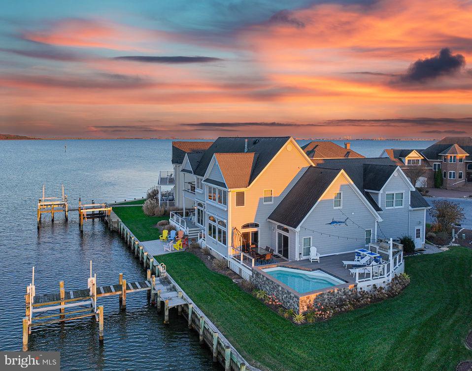 Welcome to your WATERFRONT OASIS! This exceptional Coastal Style home was custom designed by a premier builder/owner. It graces a spacious point lot at the end of a quiet cul-de-sac in the prestigious Tern's Landing neighborhood, offering breathtaking views of the open bay and Ocean City bridges. From the stone-adorned exterior and lush landscaping to the top-notch interior, every detail reflects a perfect blend of luxury and quality craftsmanship. The home welcomes you with a large entry foyer that immediately captivates with stunning water views.  Indulge in unique upscale features seldom found in other homes, including a separate entrance to a spacious living area over the garage - an ideal 4th bedroom or office. Enjoy the abundance of upgrades such as custom Andersen windows, coffered and raised or vaulted ceilings, and exquisite trim detailing. Each bedroom boasts its own bathroom, and all four bedrooms can be considered primary suites. Entertain and unwind on three outdoor decks, a patio, and a front porch, or take a dip in the inground pool, complete with a bench seat where you can relax with a drink and enjoy the water views. Grill up a storm with the built-in grill, and rest easy knowing the property is hurricane-ready with its shutters.  A separate formal dining room adds an elegant touch. The Geothermal heating and cooling system ensures energy efficiency, providing substantial savings. The property is meticulously maintained, with a lawn irrigation system, and an encapsulated crawl space for added protection. Situated on a spacious point lot at the end of a quiet cul-de-sac, this home provides an ideal setting. This home is SOLD FULLY FURNISHED and ready for your immediate enjoyment! Explore the amenities of Ocean Pines, including the Yacht Club and restaurant, 5 swimming pools (one enclosed), a Robert Trent Jones golf course, marina, Community Center, Beach Club on the ocean, community police and fire departments, dog park, playgrounds, walking/biking trails and a racket center with pickleball courts. Embrace the coastal lifestyle with this extraordinary residence!