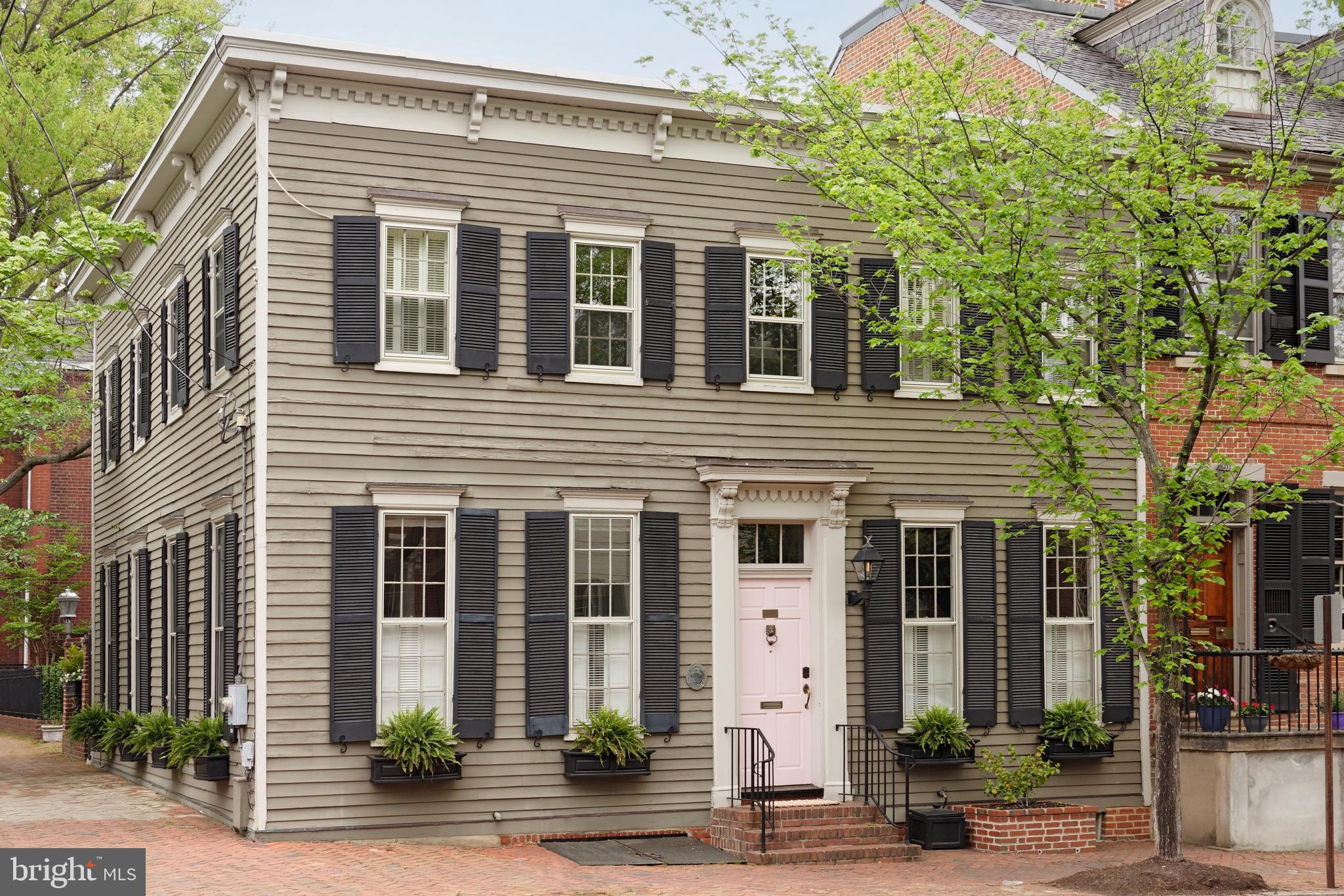 This spacious corner house in the Southeast Quadrant offers immense natural sunlight from three sides.  Built in 1842, this historic home features original heart pine floors, nine over nine pane tall windows and eleven-foot-high ceilings, two stunning archway entrances grace the living room along with beautiful millwork.  An original exposed brick wall offers texture and interest in the long dining room, perfect for entertaining.  A hyphen hallway ushers you into the bright family room, perfect for TV watching, and  French glass doors open to the patio garden.  Culinary enthusiasts will love the kitchen renovation with careful attention to every detail including the Bertazzoni stove, Bosch dishwasher, Sub-Zero refrigerator, custom cabinetry, and coffered ceiling.  Enjoy meals sitting by the windowed eat-in area or at the island and admire the handsome gas fireplace with an original carved mantel.  The glass French door connecting the kitchen to the tranquil flagstone patio garden creates a seamless indoor-outdoor flow, perfect for hosting outdoors in warm weather. A powder room with sophisticated wallpaper is convenient and accommodates guests.  
Sleeping quarters reside upstairs and provide a peaceful place to unwind and relax. The light-filled primary suite is delightful featuring bookshelves, skylight, and a walk-in custom closet.  Find your zen in the renovated spa-like primary bath with a free-standing tub, steam shower with seamless glass door, marble top vanity, skylight, and exposed brick wall.  Two spacious bedrooms are beautifully appointed with ample closets and many windows.  An updated full bath with a seamless glass shower, laundry, and additional storage completes the second floor. 
The versatile lower level can be utilized for storage or it can be transformed into a workout space with exercise equipment or yoga mats.  It is a practical and appealing extension of this wonderful home. A prime Old Town location offers an idyllic living experience with convenient access to shops, restaurants, parks, and the waterfront.