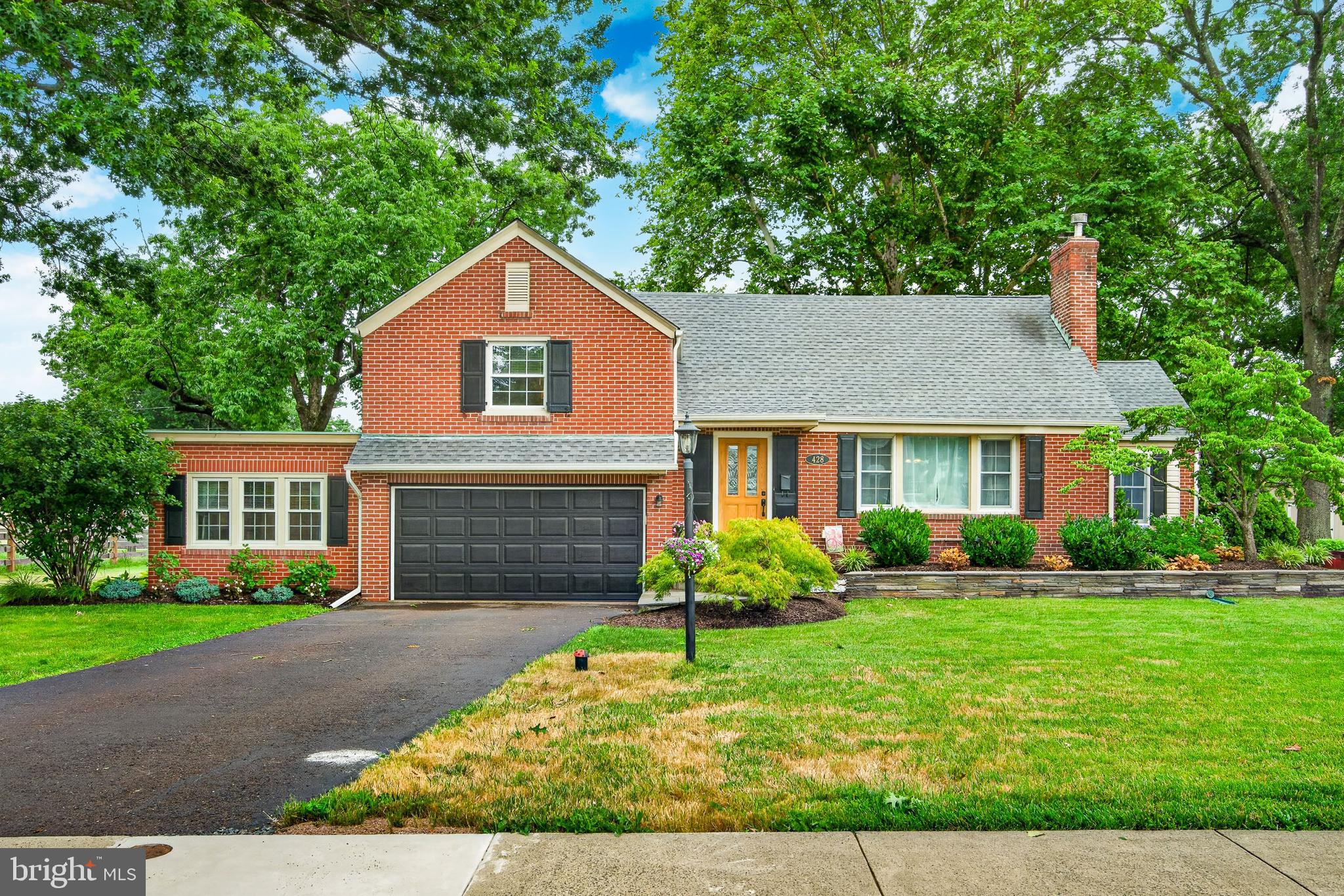Welcome to this charming split-level home in the heart of Souderton Borough, where timeless 1940s craftsmanship meets thoughtful modern updates. Tucked away on a quiet, nostalgic street and situated on just over a quarter-acre lot, this inviting property offers the perfect place to call home. Step inside the welcoming foyer featuring luxury ProGen vinyl plank flooring, which leads into a comfortable living room filled with character. Large windows flood the space with natural light, while custom built-in cabinetry showcases the home's original charm. A fireplace with a wood stove insert adds warmth and ambiance, making it the perfect gathering spot on chilly winter evenings. The well-appointed kitchen is designed for both everyday living and entertaining, featuring a built-in double wall oven, cooktop and microwave along with a GE dishwasher, granite countertops, a large stainless-steel basin sink, ceramic tile backsplash and abundant cabinetry. The kitchen flows seamlessly into the dining room and an additional window-lined sitting room that overlooks the beautifully manicured backyard. The second floor offers two spacious bedrooms and an updated hall bathroom with double sinks. Occupying the entire third floor, the private primary bedroom provides a peaceful retreat complete with three large closets. The lower level offers exceptional versatility, including a laundry area with a private bathroom, a one-car garage currently utilized as an exercise room and an additional office or multi-purpose space. Additional garage space provides room for two small vehicles. There is also substantial unfinished space housing the utilities, along with a sump pump and French drain for added peace of mind. Comfort and efficiency are enhanced by multiple heating zones and three heating options, including an oil burner, electric heat pump in addition to the wood-burning fireplace. Filled with warmth and character, this Souderton home combines thoughtful updates with exceptional functionality in an inviting atmosphere you'll love coming home to.