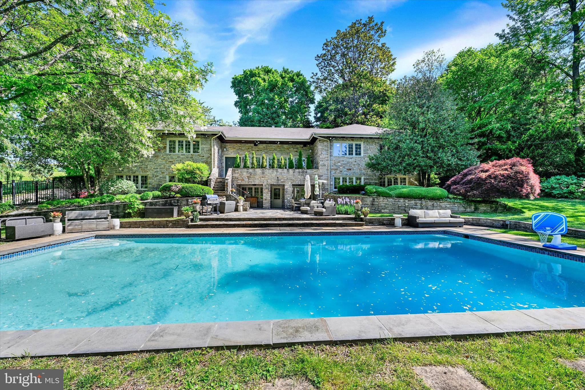 Perched high on a secluded hilltop, this massive stone estate is a rare opportunity in the heart of historic Roland Park. As you travel up the private driveway, you are welcomed into your own leafy sanctuary situated on nearly a full acre of beautifully landscaped grounds. 
  
The spectacular outdoor space immediately impresses with a large in ground swimming pool surrounded by mature trees, lush lawn areas, and multiple spaces designed for entertaining and relaxation. An outdoor kitchenette complete with sink, refrigerator, and cabinetry makes hosting effortless while the whole house entertainment system enhances both indoor and outdoor gatherings. A convenient powder room with direct access from the pool area adds additional functionality for outdoor entertaining. 
  
Step inside and prepare to be amazed by the sheer size and character of this extraordinary home. With 7 bedrooms, 4 full baths, and 3 half baths, including a private in law suite, there is room for extended family, guests, multi generational living, or flexible work from home arrangements. 
  
The lower level features a private in law suite with its own separate access from the garage and accessibility features including multiple grab bars and an accessible style bathroom. This exceptional space includes a full kitchen, family room with a gas fireplace, laundry room, 2 bedrooms, 1 full bath, and 1 half bath, making it ideal for extended family, guests, caregivers, or private living quarters.  
  
The home is filled with expansive living spaces, intricate built ins, and timeless architectural details throughout. The spacious living room features a beautifully tiled gas fireplace, adding warmth and character to the home’s inviting atmosphere.  A dedicated office with extensive built ins provides an ideal space for working from home, studying, or managing everyday household needs. All bathrooms throughout the home have been beautifully updated, including heated floors in both primary bathrooms.
  
The gourmet kitchen is truly a showstopper with expansive countertops, abundant cabinetry, and a large butler’s pantry complete with additional storage, main floor laundry, and undercounter wine and two drawer refrigerators. The adjoining dining room easily accommodates large gatherings and holiday entertaining. 
  
This one of a kind estate combines privacy, luxury, and functionality in an unbeatable location close to I 83, Mt. Washington, Towson, shopping, dining, and more. Schedule your private tour today and experience everything this exceptional property has to offer.
