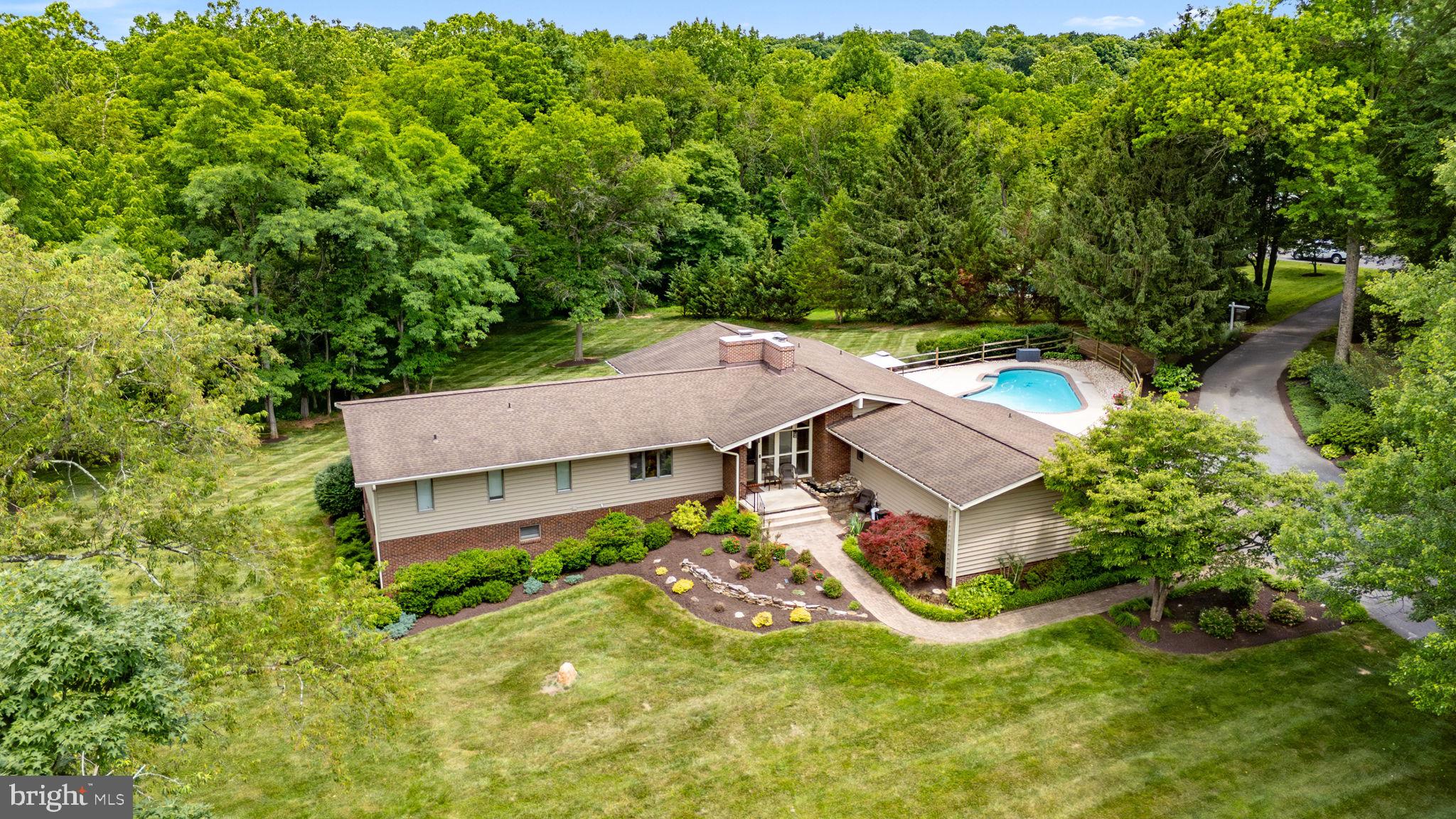 A private contemporary retreat on over five picturesque acres in the heart of Woodbine! This exceptional property offers the perfect blend of peaceful country living and modern convenience with 6 bedrooms, 4 full bathrooms, an expansive open floor plan, no HOA, and endless opportunities to enjoy both indoor and outdoor living.

From the moment you step inside, you'll appreciate the soaring cathedral ceilings, exposed wood beams, abundant natural light, and beautiful hardwood floors that create a warm yet dramatic atmosphere. The thoughtfully designed mudroom provides everyday convenience with a main-level laundry area, full bath ideal for pool guests, butler's pantry with granite countertops, and direct access to the attached two-car garage.

The beautifully updated kitchen is the heart of the home, featuring black stainless steel appliances, Silestone countertops, Ceramic flooring, with an open concept to the Family Room featuring a cozy wood burning stove, vaulted ceilings with exposed beams, and picturesque views overlooking the resort-style backyard. Whether hosting family gatherings or quiet evenings at home, this space was made to be enjoyed.

The spacious living room showcases floor-to-ceiling windows, filling the home with natural light, along with a second wood-burning fireplace and sliding glass doors leading to a large private balcony where you can relax and take in the breathtaking views of the surrounding countryside.

The main level also features four generously sized bedrooms, including an impressive primary suite with a large walk-in closet and a luxurious en-suite bath complete with a jetted soaking tub, double vanity, and separate shower. Two beautifully renovated bathrooms (2019) offer today's finishes, including quartz countertops, double vanities, and a custom multi-jet rain shower.

The finished walkout lower level expands your living space with two additional bedrooms, a fourth full bath, an oversized family room with recessed lighting, Bose surround sound, access for a 3rd fireplace or wood/Pellet stove, abundant storage, and direct access to the private patio and backyard oasis.

Step outside and experience your own private resort. The spectacular lagoon-style heated in-ground pool is surrounded by mature trees and lush landscaping, creating the perfect setting for summer entertaining, weekend relaxation, or simply enjoying the peaceful surroundings.

Significant updates include a new roof, and new siding with stone accents (2017),  renovated bathrooms (2019), well pump (2024), chimney cap (May 2026), and fresh professional landscaping (June 2026).

Offering the privacy of country living while remaining just minutes from major commuter routes, shopping, dining, and top-rated Howard County amenities, this one-of-a-kind property truly offers the best of both worlds. Be sure to explore the virtual tour and experience everything this remarkable home has to offer.

Privacy. Space. Stunning views. Resort-style amenities. This is more than a home—it's a lifestyle."