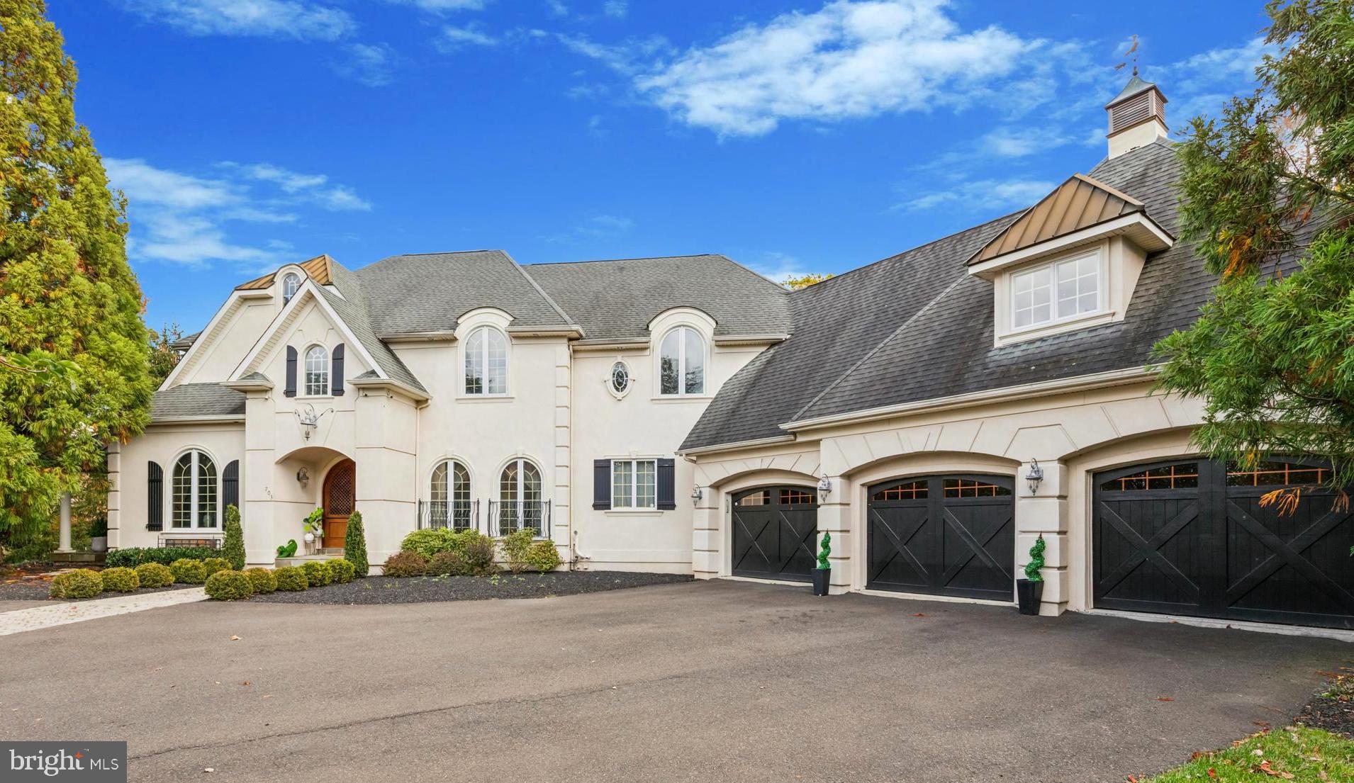 Welcome to an extraordinary custom-built residence within the highly coveted Greystone Development in Horsham Township. Nestled on a beautifully landscaped 1.57-acre lot, this distinguished 6,427 sq ft residence offers an unparalleled combination of sophistication, comfort and refined amenities.
Enter through an exquisite arched wood entry door into a striking two-story foyer with inlaid hardwood flooring and custom millwork—an elegant prelude to a home where craftsmanship and precision abound. A sumptuous home office, appointed with built-in bookshelves and oversized windows, and a formal dining room with rich woodwork and adjoining French doors to a private patio set the tone for refined living. The expansive great room boasts dramatic floor-to-ceiling windows, a dazzling custom wood ceiling, hardwood floors and fireplace—designed both for impressive entertaining and comfortable everyday living.  The gourmet kitchen is a chef’s dream with premium custom cabinetry, granite countertops, top-tier stainless-steel appliances including a 6-burner induction (or gas) range with pot-filler, double ovens, a generous island with seating, and a sunlit breakfast room that opens to an expansive deck overlooking the lush grounds.   A sumptuous first-floor primary suite features a spacious adjoining sitting room, dual walk-in closets (“his” and “hers”), and a spa-inspired bath with free-standing soaking tub, separate oversized custom tiled shower and dual vanities.  Adjacent is a well-appointed laundry/mud drop zone that leads to the oversized three-car garage. A tastefully finished powder room completes this level.
Ascend to the bright upper level loft landing that overlooks the foyer and leads to two generous ensuite bedrooms—each with its own full bath and walk-in closet—and a flexible sitting/office area with built-ins and Juliet balcony that is deal for a quiet retreat or additional workspace. 
The fully finished walk-out lower level elevates this home into a true resort-style lifestyle asset. Highlights include a full bar with seating, a spacious family room with fireplace, a dedicated media/theater room, an exercise room, a game/craft/entertainment room with wine fridge and butler-pantry, plus a full ensuite bedroom with bath—perfect for guests, in-laws or extended-stay accommodations.  French doors open directly to your private resort-style backyard, where every detail invites relaxation and entertainment. A sparkling heated inground pool with elegant stone coping serves as the centerpiece, surrounded by a multi-level bluestone patio perfect for sunbathing, outdoor dining, or hosting summer gatherings. The professionally landscaped grounds provide privacy and natural beauty, while a spacious deck off the kitchen offers additional seating and panoramic views of the property. Whether lounging poolside, entertaining guests, or enjoying  a quiet evening under the stars, this backyard transforms every day into a vacation at home.
The end of the cul-de-sac locale enhances the sense of exclusivity and privacy.  Ideally located within the Hatboro-Horsham School District, this estate combines serene suburban living with easy access to downtown Ambler’s boutiques, cafés, and train station, as well as nearby golf courses and major commuter routes including Route 309 and the PA Turnpike.
703 Daventry Way is more than a home — it’s a statement of elegance, superior craftsmanship, and luxury living. Every space has been thoughtfully designed to deliver comfort, sophistication, and a resort-inspired experience right at home that bestows a remarkable lifestyle for the discerning buyer!