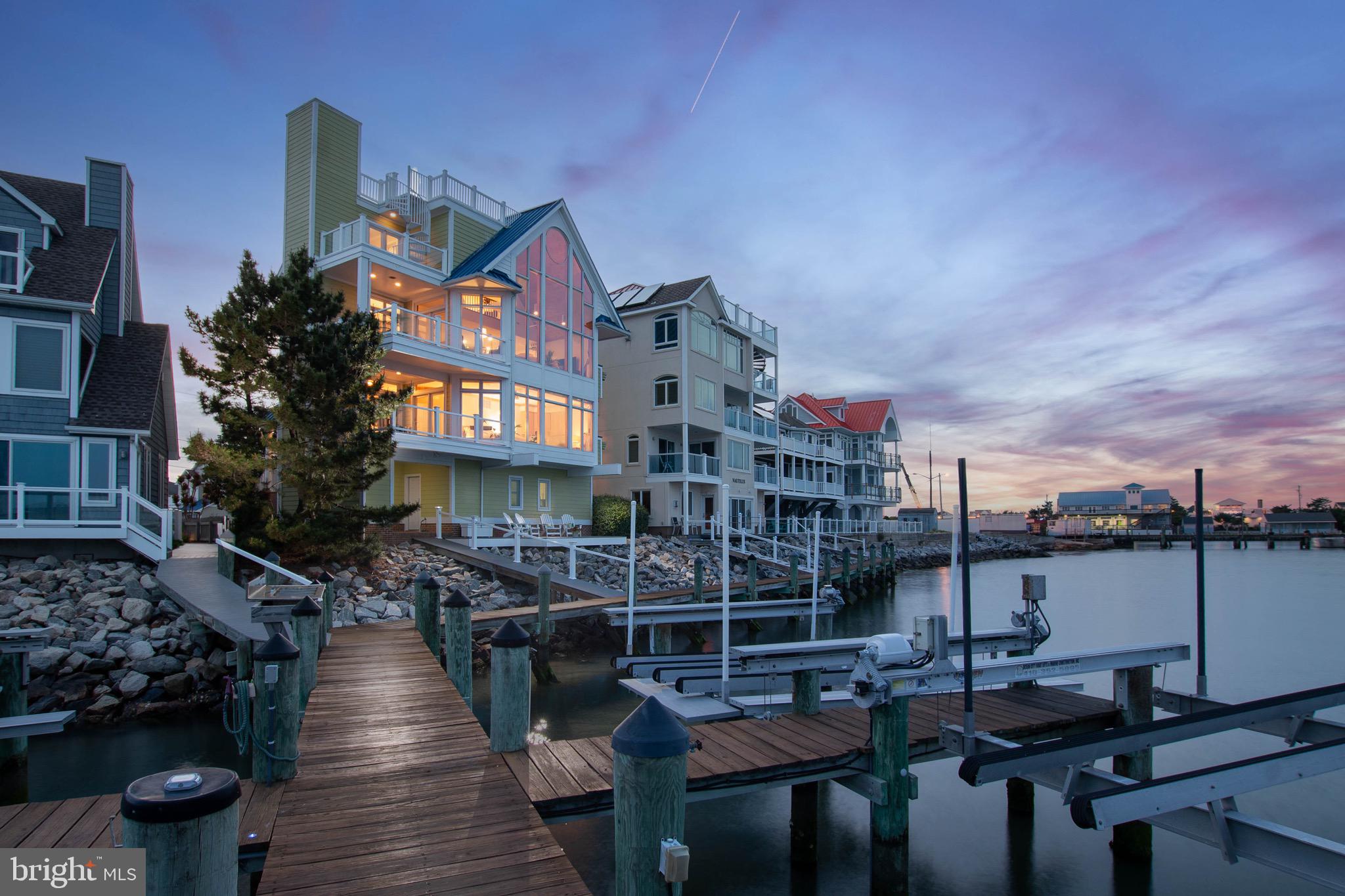 If real estate truly comes down to location, this West Ocean City setting is difficult to top.

With expansive water views, direct boating access, and a front-row perspective of the inlet, Assateague, and the Ocean City skyline, this 4-bedroom, 4-bath home stands out in one of the region’s most desirable coastal locations.

Custom built in 2003 and designed to capture the full impact of its surroundings, the home features breathtaking views from multiple levels, an open kitchen and living area wrapped in glass, generous bedroom spaces, two fireplaces, and an elevator serving every level, including the rooftop deck.

The main living area is the centerpiece of the home, bringing the kitchen, dining, and living spaces together in one bright, open gathering space designed around the water.

The primary suite is a standout of its own, with generous space, beautiful natural light, a perfectly positioned fireplace, and the same incredible water views that define the home. A remarkable custom bathroom and additional walk-in dressing room/closet complete the suite with comfort, function, and style.

The outdoor spaces are just as impressive, with five separate seating areas including covered and uncovered balconies, a waterside deck, and a rooftop deck with sweeping views across the bay, inlet, Assateague, and Ocean City. Whether you are entertaining, relaxing, or watching the boats move through the water, the setting is always part of the experience.

For boating, the property includes two deeded boat slips with lifts, giving you direct and immediate access to the surrounding waterways. The location also places you close to restaurants, marinas, beaches, shopping, entertainment, and the best of coastal Maryland.

This is a rare opportunity to own an exceptional waterfront home in one of West Ocean City’s most memorable and hard-to-duplicate locations.