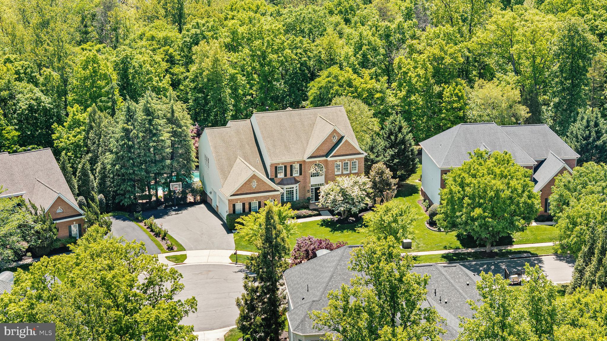 On the banks of scenic Goose Creek, this impressive estate of significant influence awaits in a highly exclusive cul de sac in the community of Lansdowne on the Potomac. A stately brick colonial home combined with a private pool on a premium lot all backing to mature trees for exceptional seclusion is simply unmatched for this community. Lush landscaping framed with stately colonial architecture as the home greets you with a dramatic double height foyer with sweeping stairs and art quality lighting. The entrance flows seamlessly across the formal dining room with butler’s pantry, private reading library, home office, sunroom and enlarged gathering room. Guests will be awestruck by sunlight beaming in through an abundance of views from the windows as this path will lead to the open concept chef’s kitchen. In the timeless chef inspired kitchen, create best-loved recipes with the help of professional grade Viking and Sub-Zero appliances. Guests and family alike will adore savory holiday meals in the dining room, and joyful brunches in the luxurious sunlit breakfast room. From the kitchen, a meticulously framed ceiling will guide and delight as you explore the 7,600+ sq. ft. home. Intimate conversations and splendid gatherings alike are yours to host within several irresistible living spaces, while the main level study provide privacy for remote work, you can also relax in the reading room during the evenings with a book. Beautiful detailed hardwood floors will escort you to the home’s second level where the grand entrance offers views of dewy mornings and the meticulous landscaping. In the evenings, spacious bedrooms and spa-like bathrooms allow family and guests to unwind. In the primary suite, choose to relax in the dual shower or with an evening of bubbles in the regal soaking tub. Afterwards, your sitting-room with a miniature tea/wine bar beckons you to continue plans of blissfully hiding away. A elegant primary retreat with a spacious custom closet featuring tailored shelving and an exclusive second story balcony with tranquil poolside views offer an easy escape from a busy day. There’s no shortage of entertainment and pampering as the home offers movie nights in the theater, a lower level parlor, wine-tasting bar, home gym, crafts/hobby area, sports viewing room, pool/ping-pong table room and featuring a floor to ceiling cedar-lined storage room to store designer luxury goods. A lower level bedroom can be ideal for extended guests. As you approach the exit to the garage, an expanded mudroom with ample shelving for week long activities leads to a main level deluxe laundry room, complete with a concierge style high end steam closet for dry cleaner quality care for delicate clothing. Outside, a 3 car side load garage ensures effortless daily access and abundant space for vehicles and storage, combining convenience with refined functionality. Treat your guests to sunny afternoons by the pool and moonlit evenings near your custom outdoor wood burning fireplace. The residence features a sophisticated, multi-tiered surround sound system integrated throughout both the interior living spaces and the exterior pool area, delivering an exceptional audio experience designed for elevated entertaining. As a member of the community, you’ll enjoy access to the exclusive Potomac Club, which offers swimming, tennis, billiards, gym membership, and event space. In addition, membership is available at the nearby Lansdowne Resort, which offers golf, spa services, and fine dining. Refresh your mood and connect to nature via the area’s numerous hiking trails, or choose to go boating and fishing on the Potomac River or Goose Creek. Nearby historic downtown Leesburg offers posh farm-to-fork restaurants, boutique shopping, and town festivals. Further afield, Washington D.C. will entertain with urban flair, and nearby Dulles International Airport awaits to transport you anywhere in the world!