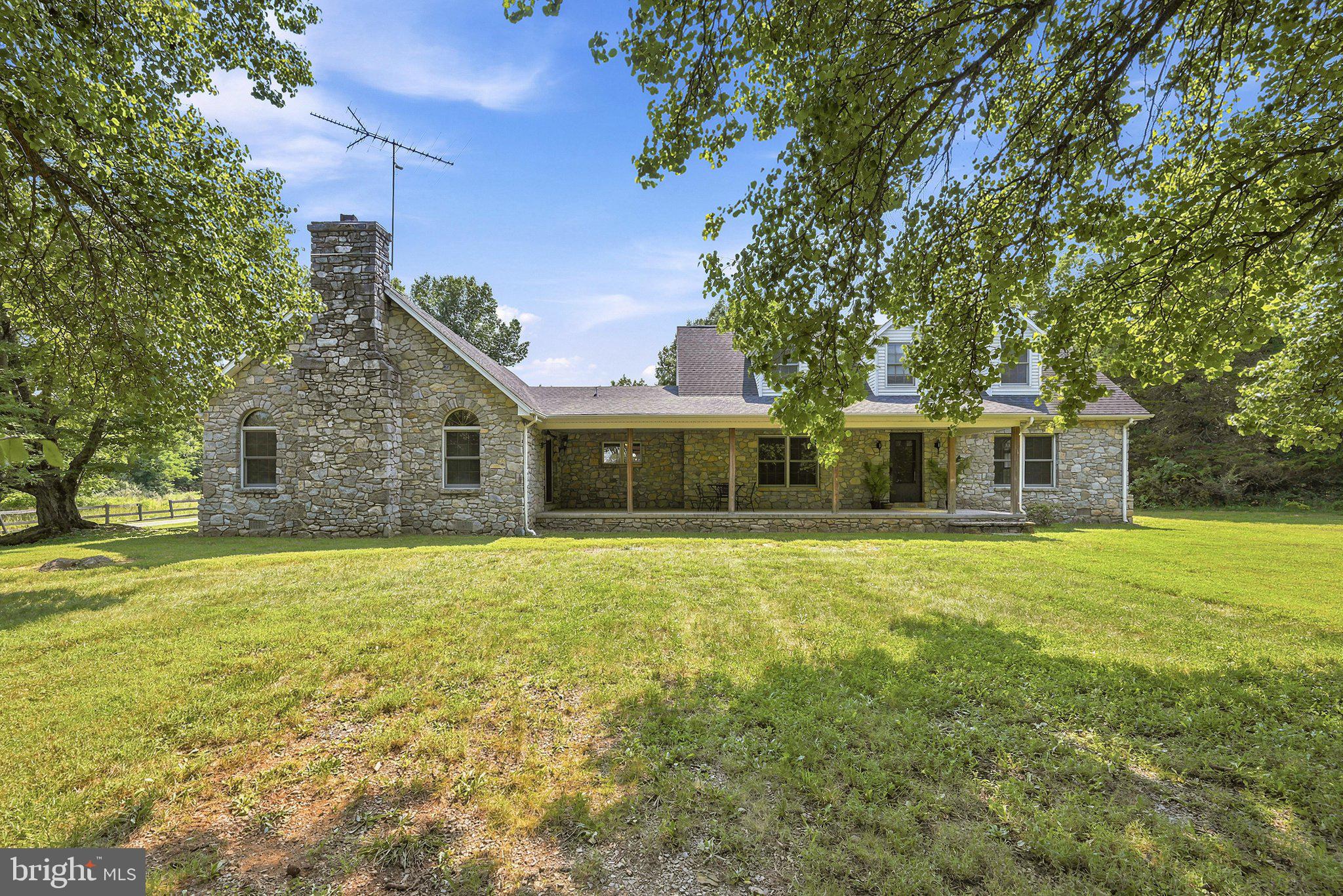 Welcome to "Stoneland", a 4,338 sq.ft. sprawling stone fronted country cape cod on 6+ acres. Minutes to Berryville, we are proud to bring you this incredible  3 bedroom, 3.5 bath home. Sitting at the end of a long private driveway surrounded by mature shade tress and a sweeping front + back open and manicured lawn. There is a main level primary featuring 2 walk in closets and large ensuite bath w/ double bowl vanity, tub/shower combo and a new seperate walk-in shower. From the primary, make your way to the formal living room/den featuring a vintage fireplace mantel from the Owner's previous childhood home! There is not only a formal dining room but also a sunny breakfast room off the kitchen with a lovely bay window. The kitchen has ample amount of cabinet space, built in wine rack + desk, wall oven and all retro applainces that are still in great shape! The family room is the star of the show here, boasting with natrual light and a stunning floor to ceiling stone fronted, wood burning fire place and access to the large front porch. There is plenty of room for any size gathering here! Off of the large family room there is a formal office area w/ double french doors. This home has two different sets of stairs to take you to each wing's upper level. From the family room, you will take the stairs to a bright, light filled sunroom! This could be used as an additonal office, bonus room, guest room, play room, or game room. Complete with a full bathroom w/ a walk-in shower, closets, and access to the  attic for additonal storage.  You will access the other upper level wing through the formal living and the flared style staircase, this will bring you to the two additonal bedrooms + full bath. Both upper level bedrooms have attic access. The main level also houses the laundry room & a half bath, perfect for guests! The front +back porches are both an ideal space for spending time together, enjoing your morning cup of coffee or relaxing after work with a beverage. The park-like yard makes it feel like a world away while still being just minutes from Berryville's ammenties. Throughout this home you will find solid wood doors, french doors between rooms, and wonderful wood work including the wood casement windows. All of the floors are hardwood or new vinyl plank. The interior has been freshley painited + the 30 year artch. roof is only 12 years old! The home has 3 HVAC zones - 2 being replaced in 2025 and two water heaters. All of the stone on the home was from the gathered from the family farm and installed by some of the best stone masons in the area. Everything you'll need can be found on the main level. The two upstairs living spaces are perfect for guests, part-time, or full-time live in family. Built by a well known local builder, this home has all of the upgrades and touches a  buyer is looking for.