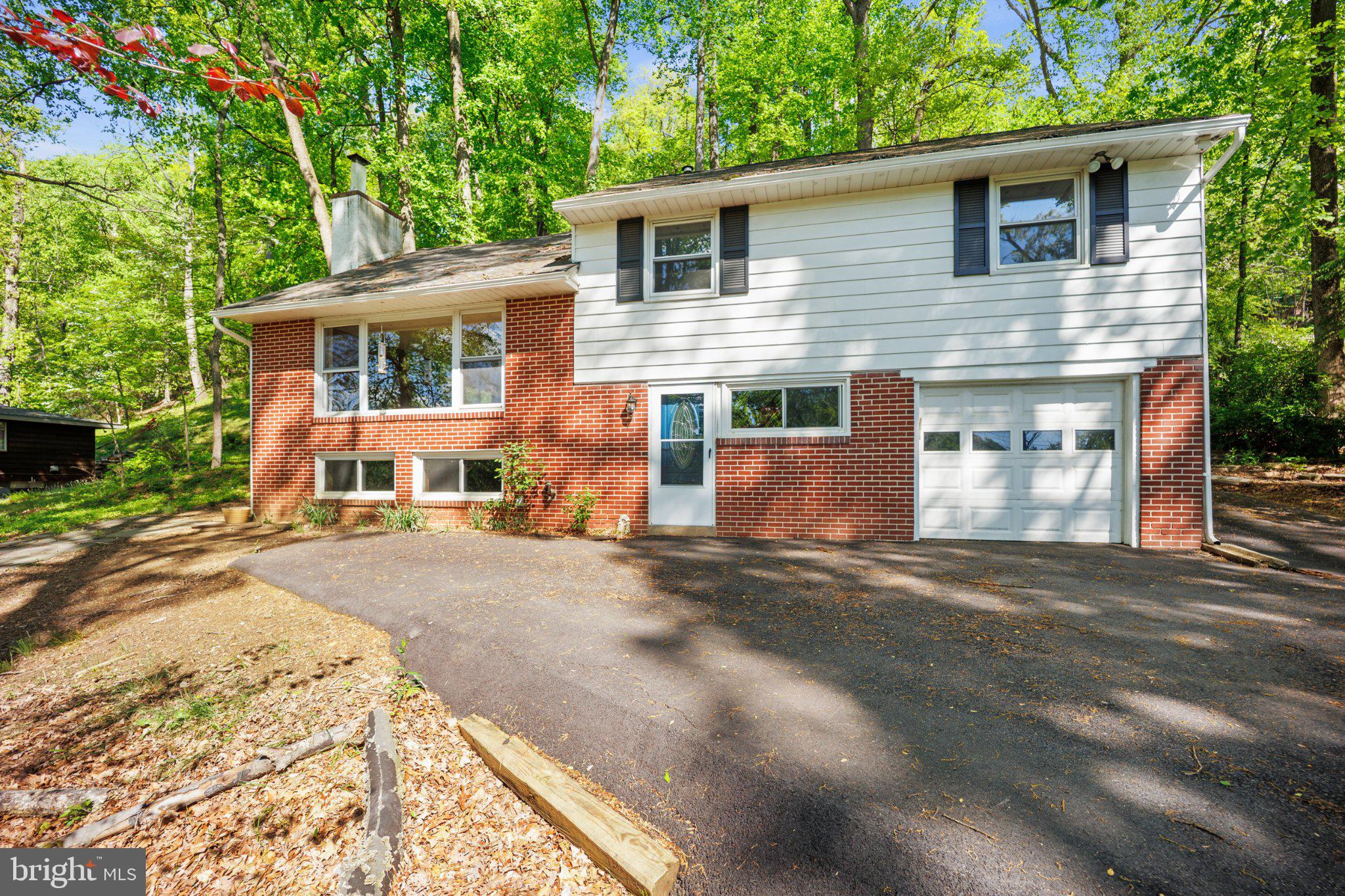 Make your appointment today!  Set on over an acre of tranquil, wooded land, this split-level home in Gulph Mills Village presents a compelling blend of traditional architecture and practical design, thoughtfully updated for contemporary living. The exterior, a classic combination of white siding with brick accents, is framed by mature trees, creating a private and established setting. The attached car garage and asphalt driveway offer convenient access, while the natural landscaping and sloping front yard contribute to the property's rustic appeal.
Inside, the home's five levels are designed to maximize both light and space. The living room, a central gathering point, features a striking wood-burning brick fireplace and a large picture window that frames scenic views, flooding the space with natural light. A spacious living room with a distinctive wood panel accent wall, complemented by recessed lighting and a ceiling fan. Throughout the main living areas, light hardwood flooring and white walls create a bright and airy ambiance.
The kitchen, while functional, provides an opportunity for future personalization. The hall bathroom has convenient access to the bedrooms, the downstairs powder room is convenient for guests, and the primary bath offers a private retreat with a shower stall. The lower level introduces a comfortable den and a laundry area with outdoor access, enhancing the home's practical flow.
With four bedrooms, including hardwood floors and a flexible space currently configured as a home theatre, this residence adapts to various lifestyle needs. The property's outdoor space, accessible from the dining area, includes a flagstone patio with a stone retaining wall, ideal for alfresco dining amidst the peaceful surroundings. Did you want to keep CHICKENS?  Perfect spot is located out of the way. The ELECTRIC fence is installed for ease of mind.
Positioned within the award-winning Upper Merion Area School District and offering quick access to major transportation routes, this home provides a balance of secluded living and urban convenience. At 121% of the city median price and significantly larger than the average King of Prussia home, this property offers substantial square footage and land, presenting a value proposition for those seeking more space and a private setting within a well-connected community. The distinct character of its split-level design, combined with its generous lot and established landscaping, offers a unique opportunity to own a property that feels both expansive and intimately connected to its natural surroundings.