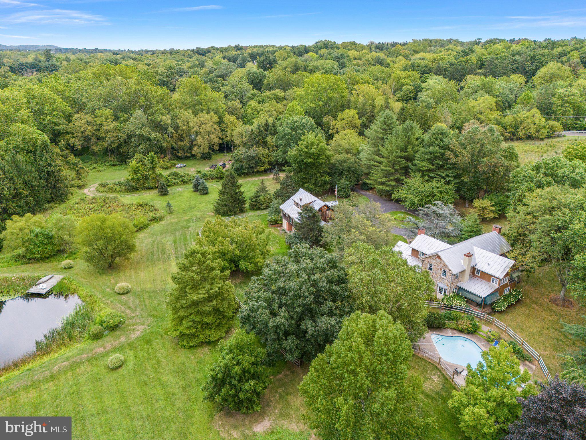 Nestled on over 19 acres across three parcels, this exquisite property offers a rare blend of privacy, charm, and modern amenities. Featuring a 3-bedroom, 2.5-bathroom Bucks County stone farmhouse, Plus a 1,000 sq ft cottage, and a wealth of outdoor features, this property is a true sanctuary in Wrightstown Twp. Built-in 1984, the main house welcomes you with a spacious front porch leading into a warm and inviting family room with a gas-stone fireplace, custom built-ins, and beautiful wide plank flooring. Just down the hall, you'll find a cozy den with a powder room and French doors opening to a private rear patio (12 x 15) that overlooks the sparkling inground pool – perfect for entertaining or enjoying a peaceful evening. The large kitchen boasts stainless steel appliances, Bucks County soapstone countertops, and a Sub-Zero refrigerator, updated in 2020. A convenient mudroom off the kitchen provides easy access to the side yard. The dining room is adorned with charming wooden beams and a wood-burning fireplace, while the adjacent office, with a private entrance, overlooks the picturesque barn. Upstairs, discover three generously sized bedrooms filled with natural light. The primary suite offers a spacious bedroom with a large ensuite bath, radiant flooring, and easy access to a walk-up attic. Two additional bedrooms feature neutral paint and lovely views from every window. The hall bath offers radiant flooring and a double-bowl vanity. The expansive grounds include a huge barn for additional storage, several sheds, a kennel with three runs, and a serene pond. The property backs to Mill Creek, offering stunning views and an abundance of wildlife to enjoy from every window. On a separate 1.86-acre parcel, the charming 1,000 sq ft cottage includes its own septic, well, and electrical systems. Inside, find a full-size kitchen, a large living room with a wood-burning fireplace, a main-floor laundry area, a full bath, and a loft space. Step outside to a spacious private deck, perfect for relaxing or hosting guests. This unique property is an ideal retreat for those seeking privacy, space, and a taste of Bucks County living. Conveniently located 10 Minutes from Newtown Borough and 15 minutes from Doylestown Borough. Council Rock High School North, Newtown Middle, and Wrightstown Elementary. Don’t miss the opportunity to make 980 Mill Creek Rd your new home! Agent related to seller.