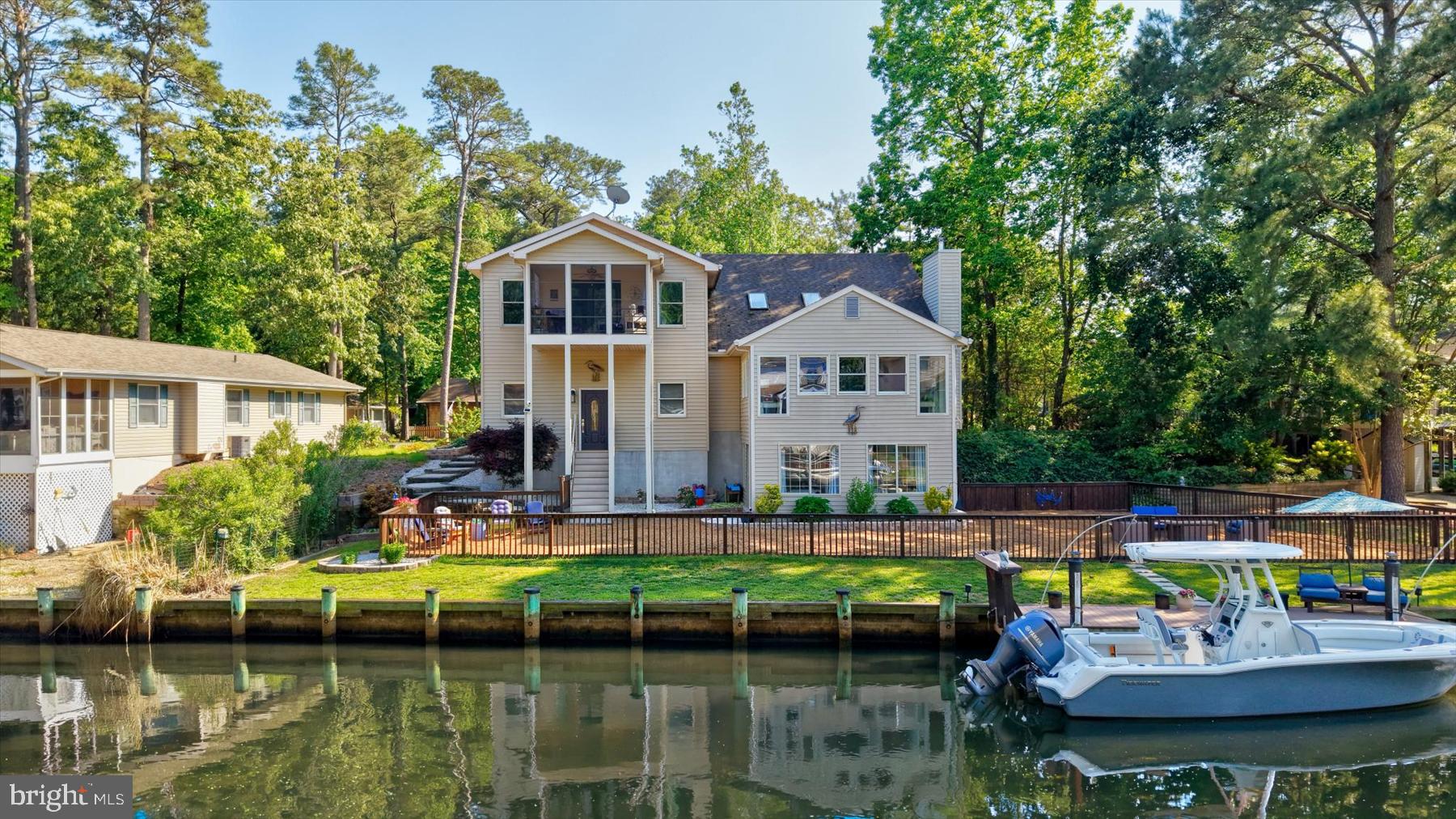 Comfort, privacy, and waterfront living come together in this fully renovated three-level contemporary home, ideally positioned along one of the quietest canals in Ocean Pines with direct access to the bay and beaches of Ocean City. Offering 4 bedrooms, 3.5 baths, and approximately 3,250 square feet, this exceptional residence has been thoughtfully updated to provide the perfect blend of coastal comfort, functionality, and entertaining space.   Designed with an open-concept layout, the home features soaring vaulted ceilings, skylights, and expansive windows that fill the interior with natural light while showcasing tranquil water views from all three levels. Multiple gathering areas throughout the home allow family and guests to comfortably spread out, including a spacious great room, waterfront den, and bar area adjacent to the kitchen.  The middle level also offers a private guest suite with en suite bath for those wishing to avoid stairs, an additional powder room, laundry room, and direct access to the oversized multi-car garage with front and rear access points.   Upstairs, the primary suite serves as a true private retreat, spanning approximately 768 square feet and featuring its own three-season porch overlooking the water. This luxurious space includes a large walk-in closet, natural gas fireplace, and beautifully renovated spa-style bath complete with extensive cabinetry, dual-person Jacuzzi soaking tub, and walk-in wall-jet shower. Two additional bedrooms, two porches, and another full bath complete the upper level.   The ground level offers even more flexibility with two freshly renovated waterfront rooms ideal for entertaining, relaxing after a day on the water, or hosting the perfect crab feast. Walls of windows and sliding glass doors provide panoramic canal views and direct access to one of the largest waterfront backyards in Ocean Pines. The oversized .35-acre lot includes a full-length fenced yard, expansive private bulkhead, maintenance-free dock with fish cleaning station, hardscape walkways, and ample room for kayaking, crabbing, pets, and outdoor gatherings.  Extensive 2026 renovations include a full interior repaint, all new luxury vinyl plank flooring, carpet, and ceramic tile throughout, remodeled kitchen and baths, a fully renovated third level with dedicated mini-split HVAC system, updated plumbing and lighting fixtures, new vanities with quartz and marble countertops, updated toilets, ceiling fans, and more. Additional highlights include three-zone heating and cooling, instant hot water system, air purification system, dehumidification system, fire and alarm monitoring with cameras, oversized garage with 9-foot door for possible boat storage, and parking accommodations for up to 6+ vehicles.   The home also offers a full concrete crawlspace with convenient interior access to mechanical systems including the furnace, plumbing, dehumidifier, air purification equipment, and AirBoss controls. Pride of ownership is evident throughout, with the roof and multi-zone HVAC systems regularly cleaned and professionally serviced.   Move-in ready and meticulously maintained, this rare waterfront offering combines peaceful coastal living with convenient access to the bay, ocean, dining, marinas, and entertainment of the greater Ocean City area.