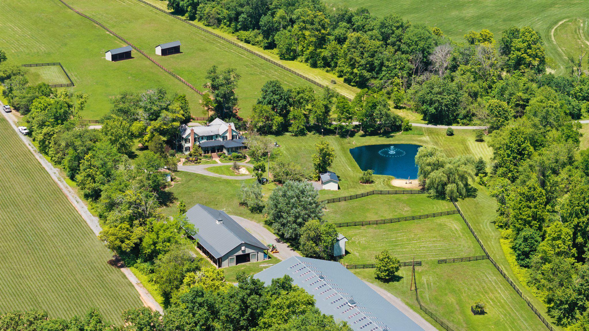 Some properties just feel special from the moment you arrive, and this is one of them.  Welcome to Foxborough Farm, a fully realized equestrian estate privately positioned across 51± acres within Montgomery County’s protected Agricultural Reserve. Offered for the first time in 26 years, the circa 1900 farmhouse was thoughtfully renovated and expanded in 2008 under the direction of architect James Gerrety, carefully preserving the home’s original architectural integrity while introducing refined craftsmanship and modern functionality throughout.  The 4-bedroom, 2.5-bath residence spans approximately 4,174 finished square feet and is thoughtfully designed to accommodate both large-scale entertaining and comfortable everyday family living. Rich architectural details define the home, including Dutch lap siding, heart pine plank flooring, reclaimed wood beams, layered custom millwork, bay and bow windows, French doors throughout, cathedral ceilings, a Seneca Stone fireplace, and a delightful sunroom featuring flagstone flooring with a distinctive steel horseshoe inlay. Subtle fox-inspired accents woven throughout the residence lend character and continuity to the home’s curated design and namesake.  A beautifully appointed gourmet country kitchen, anchored by an exceptionally long butcher block island with sink and bar seating, features high-end appliances and soapstone countertops. French doors, pocket doors, and period-inspired transom windows seamlessly connect the kitchen, butler’s pantry, dining room, family room, and custom wet bar. Expansive wraparound Trex porches accented by beadboard and skylight ceilings extend the living spaces outdoors, creating effortless indoor-outdoor entertaining while capturing tranquil views of the tiered fountain pond, fenced pastures, and surrounding landscape.  The upper level, accessed by dual staircases, is highlighted by a spacious primary suite featuring a sitting area, vaulted beadboard ceiling, spa-inspired bath with oversized walk-in shower, dual Carrera marble-top vanities, built-in storage, generous custom dressing closets, and a private bowed deck ideal for quiet morning coffee. Three additional bedrooms, a full bath with English soaker tub/shower, and a cozy sitting room complete the upper level.  Designed to support both private enjoyment and professional equestrian pursuits, the bespoke facilities are exceptional. The lighted 12-stall barn features an extra-wide center aisle, brick rubber flooring in both aisles and stalls, three foaling stalls, automatic fly spray and fan systems, hot and cold-water wash stall, tack room with half bath, feed room with heavy-duty washer and dryer, and storage for up to 1,500 bales of hay. The impressive 80’x200’ Amish-built indoor riding arena offers walls of windows, skylights, LED lighting, cross-braced wood trusses, and flexibility for both dressage and jumping disciplines. Multiple four-board painted oak fenced pastures and paddocks with extra-tall run-in sheds, along with three active crop fields, further enhance the property’s versatility while supporting substantial agricultural tax benefits.  Additional improvements include a detached guest cottage with kitchen and full bath, farm operations office with upper-level storage, and three agricultural equipment buildings. Located within an hour of Washington, DC, Poolesville offers a quintessential small-town setting with locally owned restaurants, wineries, outdoor recreation, community events, and easy access to Sugarloaf Mountain and the C&O Canal National Historical Park. The property is also located within the highly ranked Poolesville High School magnet cluster and just a short drive to the MARC Train.  We invite you to discover firsthand the rare combination of craftsmanship, natural beauty, privacy, and equestrian excellence that make Foxborough Farm a compelling full-time residence, weekend retreat, boutique equestrian operation, or enduring legacy property!