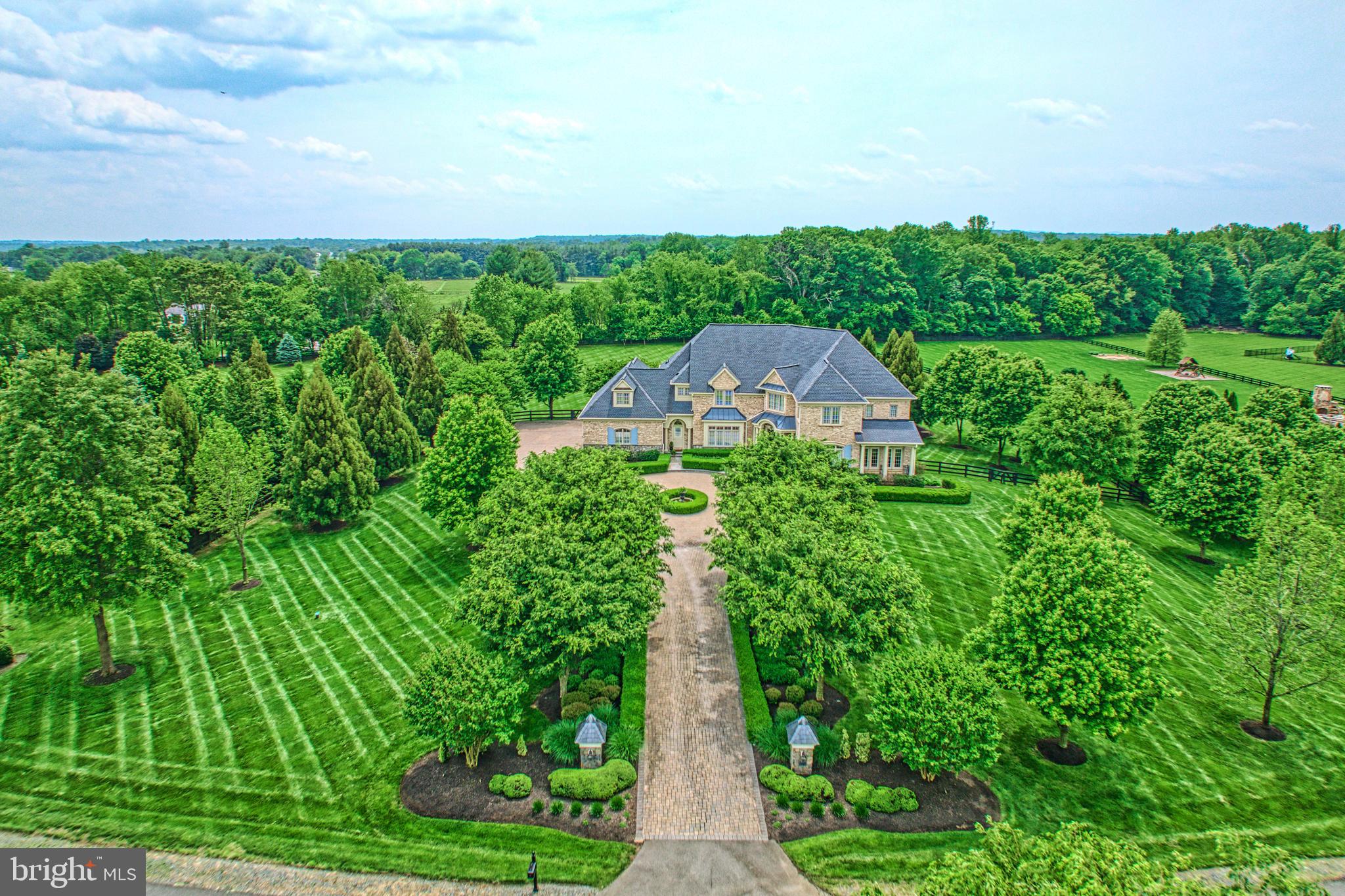Alluring with sumptuous craftsmanship and inviting charm, this 8,331 square foot executive home sits surrounded by 3.03 picturesque acres where the brick-lined drive, seasonal blooms, and refined landscapes create a setting of warm welcomes and lasting impressions. Beyond the threshold, outstanding design unfolds across living vistas where rich hardwoods and ivory hues bring comfort to premium hardware, lavish wallpaperings, and glamorous fixtures. In the centerpiece kitchen, be inspired amongst endless cabinetry, striking stonework, and professional-grade appliances; balancing tradition with contemporary edge. Here, conversations with the chef will linger over wine, while elsewhere, abundant windows cast natural light onto soaring architectural details and a picture-perfect winding staircase. Outside, join guests for al fresco fun on multiple expansive hardscapes. Serve celebrations on the sprawling deck, consider realizing pool or garden dreams within the fence-wrapped greenspace, and linger on the stone-lined patio where a fire pit, shaded koi pond, pizza oven, and covered pavilion inspire year-round-moments. Wake and refresh within six bedrooms plus over five refined baths. Settle guests within either of the lower level’s two private getaways where they’ll enjoy walk-out access, media/gym/playroom, and full bar, while within the upper-level primary, your personal oasis awaits with wet bar, sitting room, custom wardrobe, and a richly designed bath for indulgent evenings in. While on tour, visit the charming herringbone-tiled laundry, and imagine treasured rides displayed within the four-car epoxied-garage. From home, Historic Leesburg, bustling Village at Leesburg, Wegmans, commuter routes, and surrounding adventure await within greater Hunt and Wine Country.
