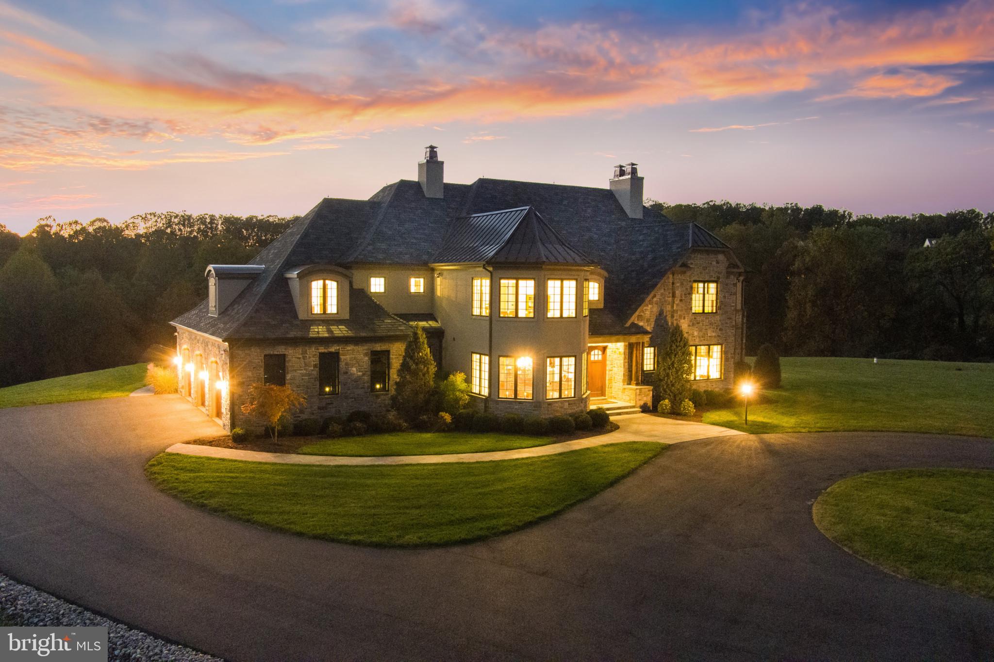 Thoughtfully curated alongside Paul Thompson of Architectural Design Works, Inc., this completely custom 4-bedroom, 5-and-a-half-bathroom private estate encompasses over 10,000 sq. ft. of living space. Ideally set on more than 20 acres, this private oasis is conveniently located just a quarter of a mile from the Baltimore County Line and minutes from 95. Upon arrival, McGuire Hill stone and solid African mahogany doors will welcome you into this rich estate which notably features wide plank hickory hardwood flooring, hand-carved cherry wood doors, reclaimed Tennessee barnwood beams and fireplace mantles. The expansive lower level with a 20-foot ceiling is enhanced with a full-swing golf simulator with the largest available screen & custom-built viewing area, a full home entertainment system by Savant Automation, and a custom wine room by Baltic Wine Cellars with large capacity mahogany storage system and real cork flooring. A 3-story elevator along with an additional custom spiral staircase, separate sauna in the primary en-suite with tailor-made German-built bench, and the list goes on and on. The westerly-facing backyard affords the most breathtaking sunsets amidst the custom-built heated saltwater pool and spa surrounded by over 3,000 sq. ft. of Travertine decking, complete with stone firepit and additional covered side patio with wood burning fireplace and screen shades. No detail was missed, nor expense spared in the nearly 2 years it took to create this impeccably maintained masterpiece. The exquisite craftsmanship and the highest quality materials available, make this home unquestionably like no other.