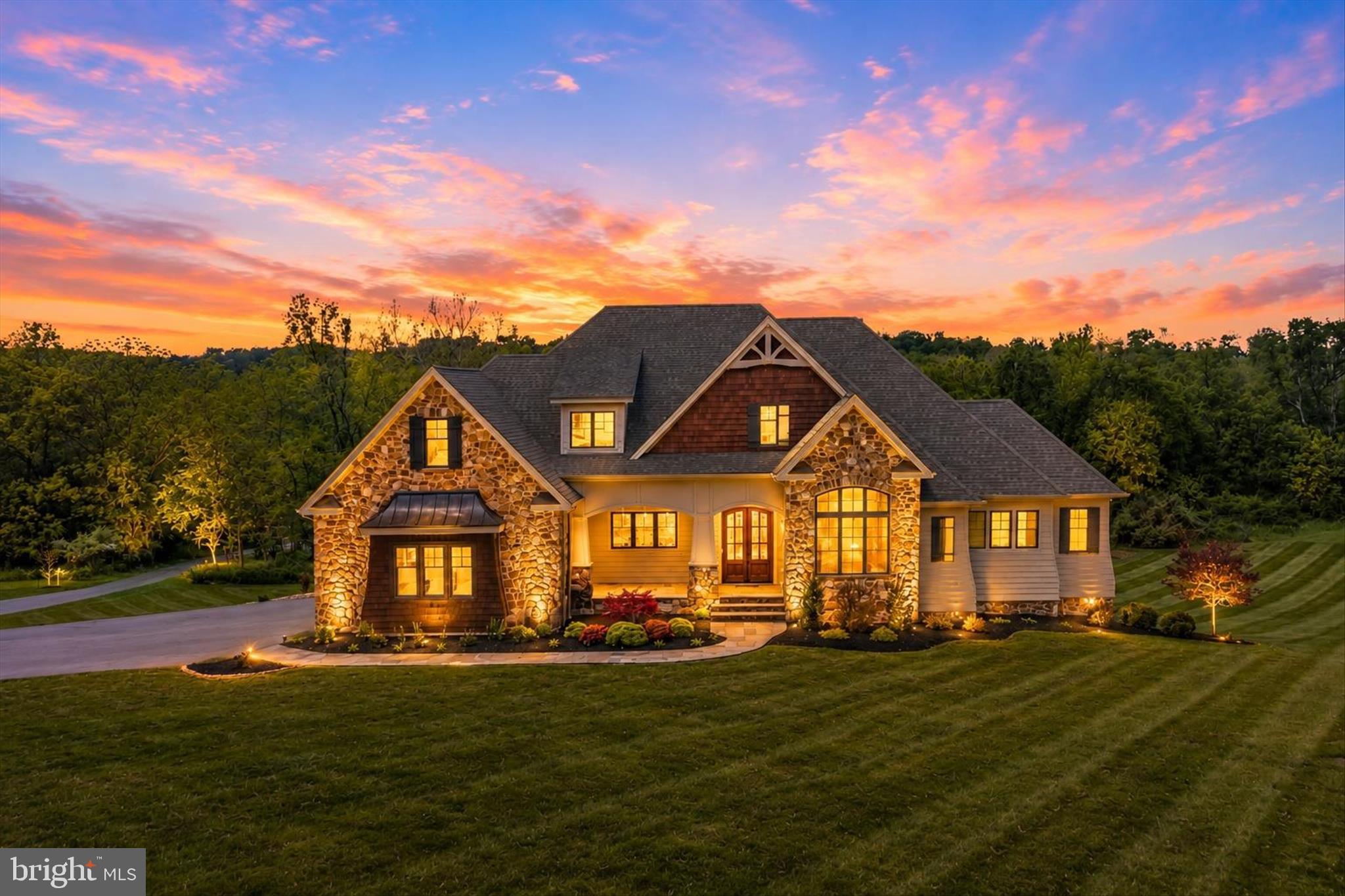 Experience the perfect blend of timeless design, luxury finishes, and natural beauty in this exceptional Craftsman-inspired estate set on 10.14 scenic acres with direct frontage on Opequon Creek. Offering nearly 6,000 finished square feet, this custom-built home features 7 bedrooms and 5 full bathrooms, including two main-level bedrooms and a luxurious primary suite designed for comfort and convenience. Life on Opequon Creek creates a setting that feels both peaceful and unforgettable. Spend your days fishing along the creek banks, kayaking downstream, or simply relaxing in one of the thoughtfully placed hammocks throughout the property. As evening settles in, gather around a firepit while enjoying the calming sounds of flowing water, open skies, and breathtaking sunsets that make this property feel like a private retreat. From the moment you arrive, the striking exterior showcases natural stone, cedar shake siding, and multiple gables that reflect the home’s quality craftsmanship and architectural character. Morning sunlight warms the front of the home, while the rear of the property captures stunning sunset views across the surrounding landscape. Outdoor living is a defining feature of the property. The expansive covered rear porch stretches the full length of the home and serves as a true extension of the living space. Anchored by one of two impressive all-natural stone fireplaces and complemented by a gas heater for year-round comfort, this elevated outdoor retreat offers the perfect place to relax, entertain, or simply enjoy the peaceful surroundings. The porch also connects directly to the primary suite, creating a seamless indoor-outdoor experience. Below, the ground-level patio mirrors the full length of the home and features the second all-natural stone wood-burning fireplace, creating another inviting space to gather while enjoying the quiet beauty of the property. Together, these layered outdoor living spaces were thoughtfully designed to maximize the views, natural surroundings, and serene atmosphere. Inside, rich dark-stained hardwood flooring and refined box trim create a warm, upscale feel throughout. The dramatic living room features soaring 20-foot ceilings and a floor-to-ceiling stone fireplace that serves as a stunning architectural centerpiece. At the heart of the home, the gourmet kitchen is designed for both everyday living and entertaining, featuring premium Thermador appliances, a 6-burner gas range, pot filler, oversized center island, custom cabinetry, and high-end finishes. The mudroom, walk-in pantry, and separate 10x10 laundry room continue the home’s elevated design with quartzite countertops and a stainless sink. The home is also fully wired with a Sonos sound system for seamless entertainment throughout. The main-level primary suite offers direct access to the covered porch and features a spa-inspired bath with a soaking jetted tub, walk-in steam shower, dual vanities, and separate his-and-her walk-in closets. A second main-level bedroom offers flexibility for guest space, office use, or additional living needs. Upstairs, a spacious loft overlooks the main living area and provides additional flexible living space. Three additional bedrooms and two full bathrooms complete the upper level, including one bedroom with a private en-suite bath. The finished walkout lower level features 9-foot ceilings, a wall of windows for abundant natural light, a spacious recreation room, two additional bedrooms, and a full bath. A dedicated media room, currently used as a golf simulator, includes a beer and wine chiller and offers endless possibilities for entertainment and recreation. Adding even more versatility, the impressive 40x60 metal building with pull-through doors includes a gas heater, full bathroom, and washer/dryer rough-in, making it ideal for hobbies, storage, workshop space, or future customization. The property also offers space suitable for horses, chickens, and select farm animals.