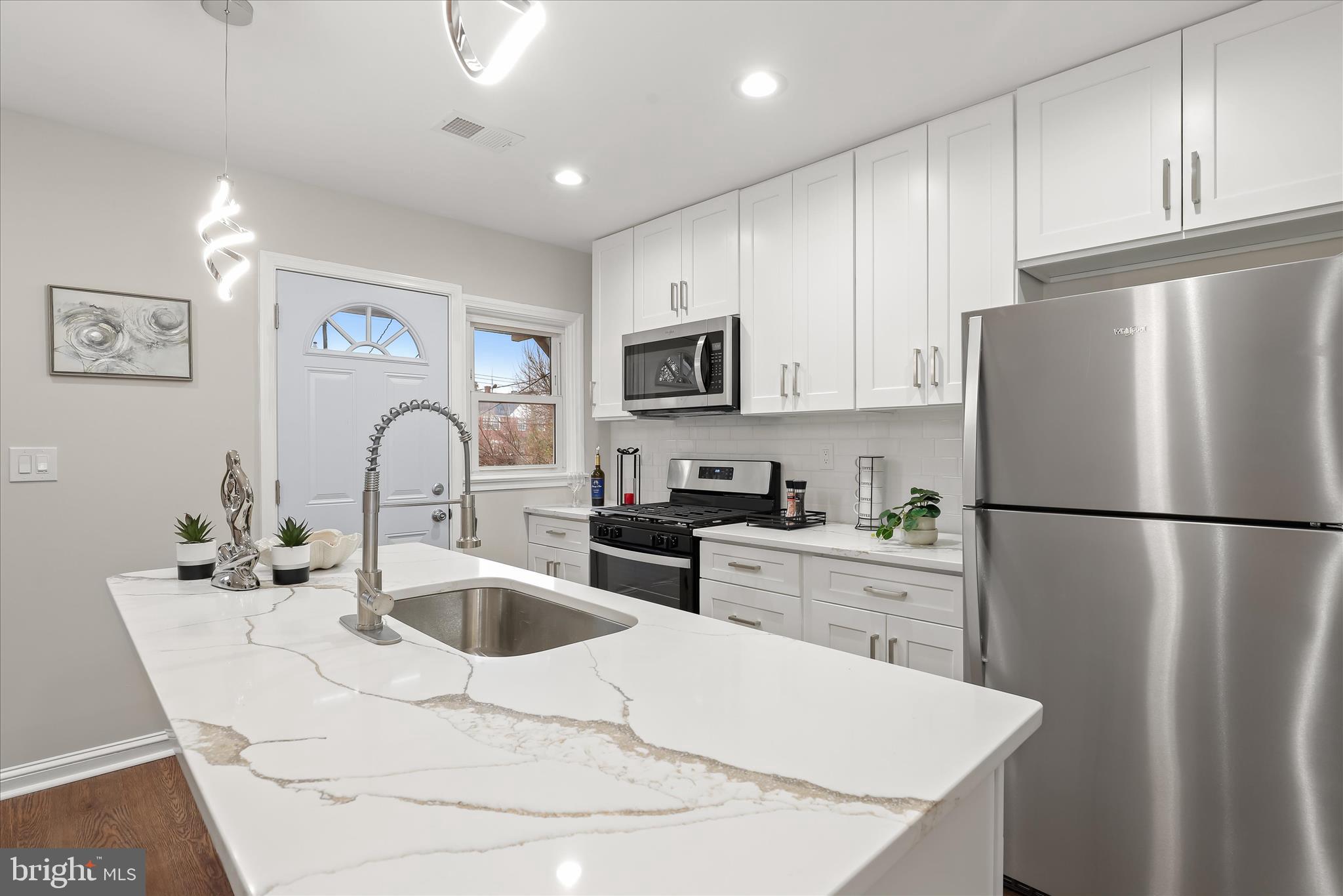 Located in the Woodbourne Heights community of Baltimore City, this interior brick townhome offers a welcoming front porch, a fenced backyard, and the convenience of a private parking pad. A newly renovated interior introduces an open floor plan highlighted by luxury vinyl flooring, recessed lighting, and abundant natural light. The living room flows seamlessly into the dining room, where a bay window overlooks the landscaped grounds and opens to the kitchen.  The kitchen is thoughtfully designed with a center island and breakfast bar, 42” cabinetry with soft-close drawers, a classic subway tile backsplash, stainless steel appliances, and quartz countertops. A main-level powder room completes the living area.  Upstairs, the primary bedroom provides a comfortable retreat with luxury plank flooring, a double-door closet, and private access to the dual-entry hall bath featuring a linen closet and a ceramic tile tub/shower combination. Two additional bedrooms complete the upper level. The fully finished lower level offers exceptional flexibility with space for two possible bedrooms, one with an en-suite bath, or the option for a home office, recreation area, and ample storage.  Enjoy proximity to Chinquapin Run Park, Loyola University Maryland, Notre Dame of Maryland University, and premier shopping, dining, and entertainment at Towson Town Center.