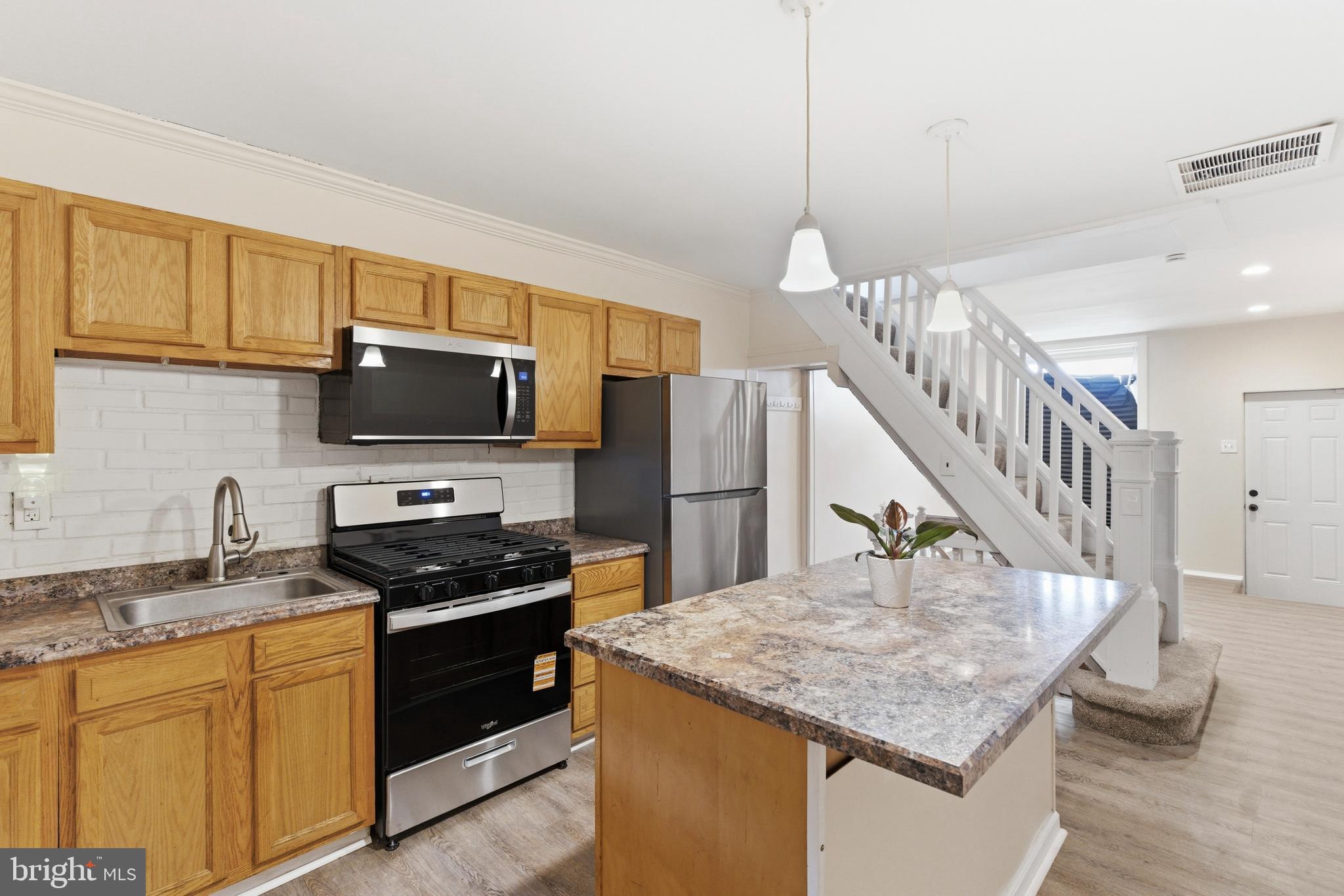 Welcome to this charming brick-front rowhome in the heart of Highlandtown, offering the perfect blend of comfort, updates, and convenience. This home is ideal for a small family or a busy professional, especially those working at Bayview, just minutes away! Step inside to find brand new flooring and carpet throughout, including durable LVP on the main level, creating a fresh and modern feel. The bright and airy living room is perfect for entertaining or unwinding after a long day. The spacious kitchen features abundant cabinetry, generous prep space, a center island for quick bites, stainless steel appliances, plus a brand new stove and microwave. Upstairs, you’ll find a light-filled primary bedroom, a full bathroom complete with a tub/shower combo and skylight, and a second bedroom that’s perfect for guests or a home office. The partially finished lower level offers a flexible rec room space along with additional storage and a laundry area. Step outside to your private, fully fenced backyard with a covered patio, perfect for hosting summer BBQs or enjoying a quiet evening outdoors. A rear parking pad ensures you’ll never have to worry about street parking. Additional perks include a low BGE bill and a location that truly can’t be beat, conveniently located near Bayview, Boston Street, Eastern Avenue, Route 40, I-895, I-95, and the tunnel, with easy access to Canton, shopping, dining, and everything the city has to offer. This move-in ready home checks all the boxes, don’t miss it!